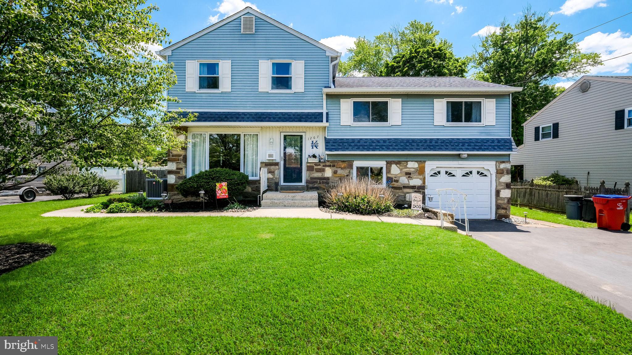 Welcome to 1267 Dahlia Road, located in the heart of Brookdale Gardens in Warminster Township. This expanded split-level home offers 4 bedrooms, 2½ baths, a one-car garage, an enormous family room addition, and an incredible backyard oasis designed for entertaining. Step inside to find beautiful hardwood flooring throughout much of the home, including the spacious living and dining rooms. The remodeled kitchen features granite countertops, peninsula, abundant cabinetry, a built-in microwave, gas cooktop, dishwasher and side-by-side refrigerator that overlooks the expansive family room. 
The impressive family room addition is the heart of the home, complete with a brick wood-burning fireplace, dedicated dining area, and full bar—perfect for gatherings large and small.  Just beyond the family room, the outdoor fun begins. Enjoy summer days on the Trex deck, relax under the covered patio, or take a dip in the heated in-ground pool featuring a waterfall. The fully fenced yard also includes a storage shed and sits on a generous .34-acre lot. The upper level offers three spacious bedrooms and a full hall bath. The private primary suite features a walk-in closet, additional closet space, built-in vanity, full bath with stall shower, and walk-up access to the attic. The lower level includes a cozy den currently decorated in Phillies fashion, a laundry room, and direct access to the one-car garage with automatic opener. Major updates provide peace of mind, including a new roof (2018), HVAC system (2023), and the majority of windows replaced in 2024 and 2025. Please note that the seller believes the public records square footage may not reflect the family room and primary bedroom additions. Buyers are encouraged to verify square footage to their own satisfaction. If you're looking for space, updates, and a backyard built for entertaining, this Brookdale Gardens beauty is one you won't want to miss.