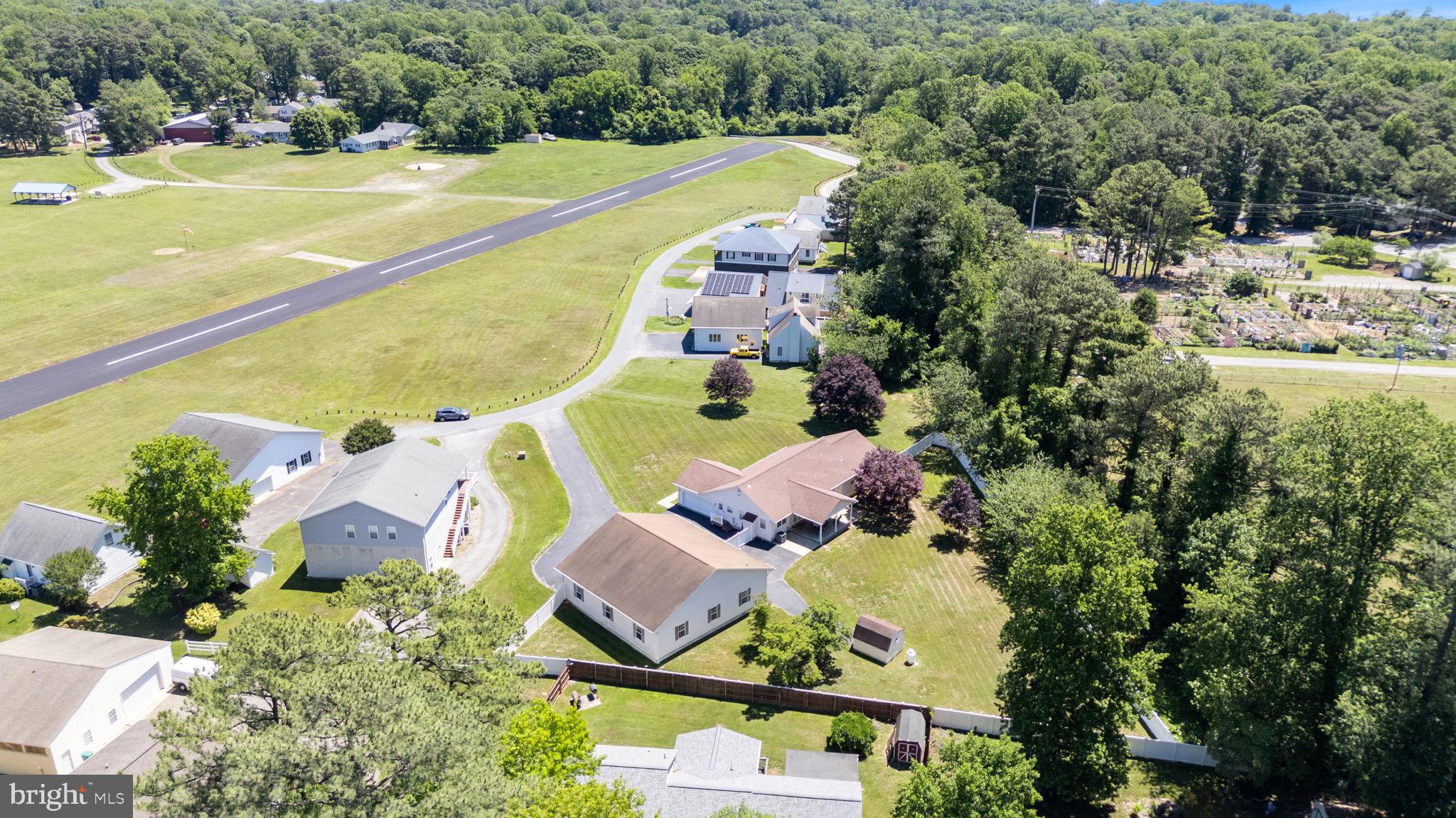 Spacious brick rambler with private airplane hanger!  Roll right out of the hanger, down the run way and off you go!  No airplane? No problem!  This outbuilding is over 2500 square feet and will hold cars, boats, campers and more!  Auto door lift and full bath included! Inside the spacious home you will find room for a crowd with the eat in kitchen complete with island, pantry, double wall oven, cook top, and more.  Family room off  of the kitchen has a fireplace for cozy evenings.  Formal dining room, living room give lots of flex space to make it what you need.  Down the hall you will find a primary suite with walk in closet, full bath with separate shower. two additional bedrooms and a hall bath.   Lower level goes on and on with a finished rec room, a storage room, exercise room, utility room, additional flex space.  Main level laundry and mud room with guest half bath leads to attached two car garage and out to the hanger.   So many extras including a full house generator, fully fenced and level back yard, covered concrete front porch, covered concrete back porch and patio making entertaining a breeze.  Not that you will need it, but there is also a storage shed!  All of this right on the airport!   Community also includes sandy beaches on the Chesapeake Bay, lake access, playgrounds, campgrounds and clubhouse.    Check out the floor plans then come check out this place!