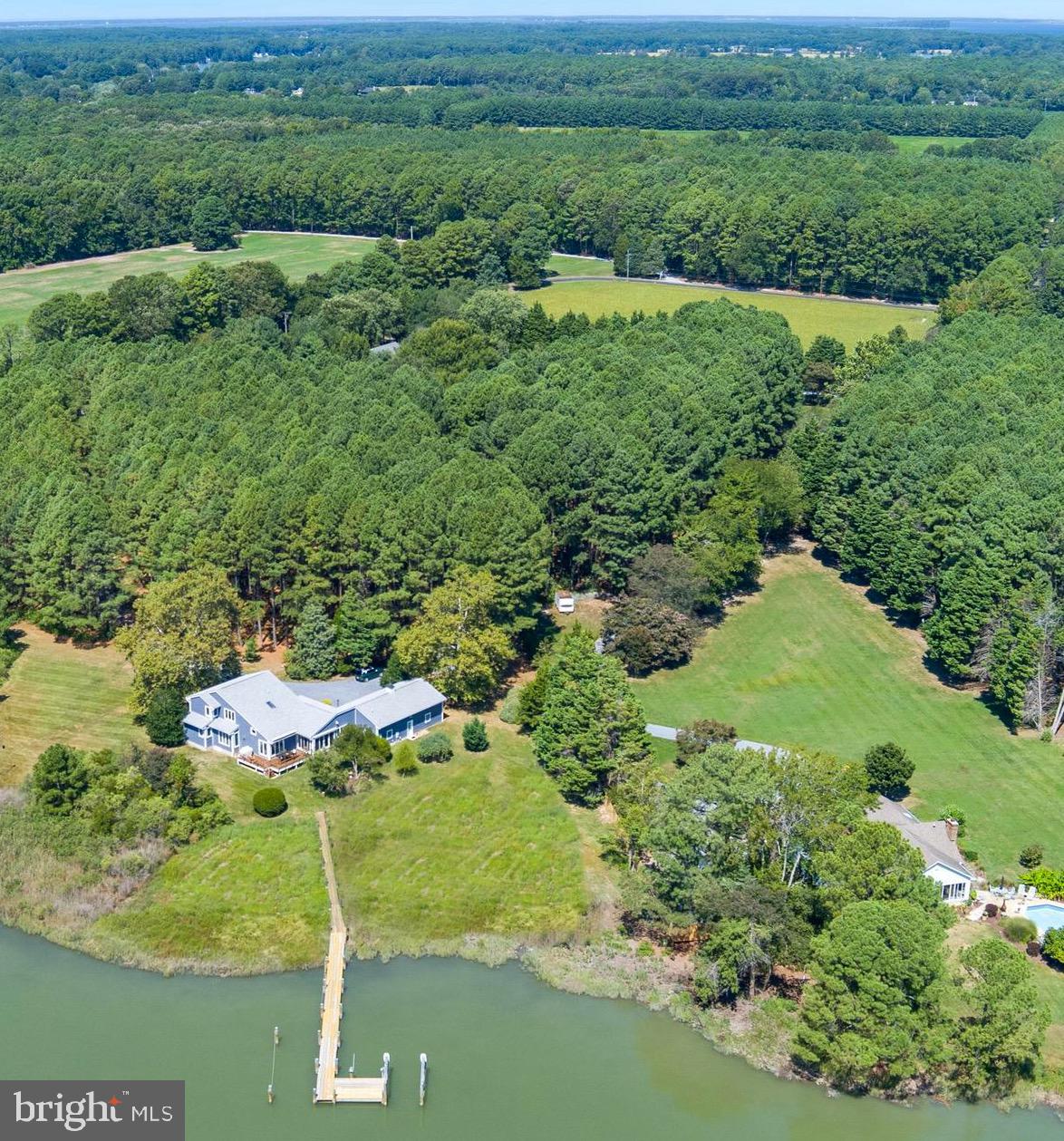 Welcome to this enchanting waterfront retreat, beautifully sited on 6.2 acres overlooking Old House Cove with scenic passage out to San Domingo Creek. Designed in a coastal style and offering 3,340 sq. ft., this 4-bedroom, 2.5-bath residence blends timeless comfort with the natural beauty of the Eastern Shore. A charming front porch sets the tone, leading into sunlit living spaces with soaring vaulted ceilings and gleaming American Cherry hardwood floors. The main-level primary suite is a serene haven with a private sitting area and spa-like bath. Upstairs, a loft lounge overlooks the living room and connects to three additional bedrooms and a shared hall bath. The gourmet kitchen, outfitted with premium appliances, flows seamlessly into the dining area, living room with cozy gas fireplace, and waterside sunroom that opens to a deck with sweeping views. A private office, versatile bonus room, and attached 2-car garage add convenience and flexibility. Outdoors, the  private pier( with electricity and water) offers two slips and electric lift,  inviting endless days on the water, while mature trees, lush landscaping, and native flora frame this idyllic setting. Countless updates further enhance this exceptional St. Michaels offering and a recent survey shows room for pool.