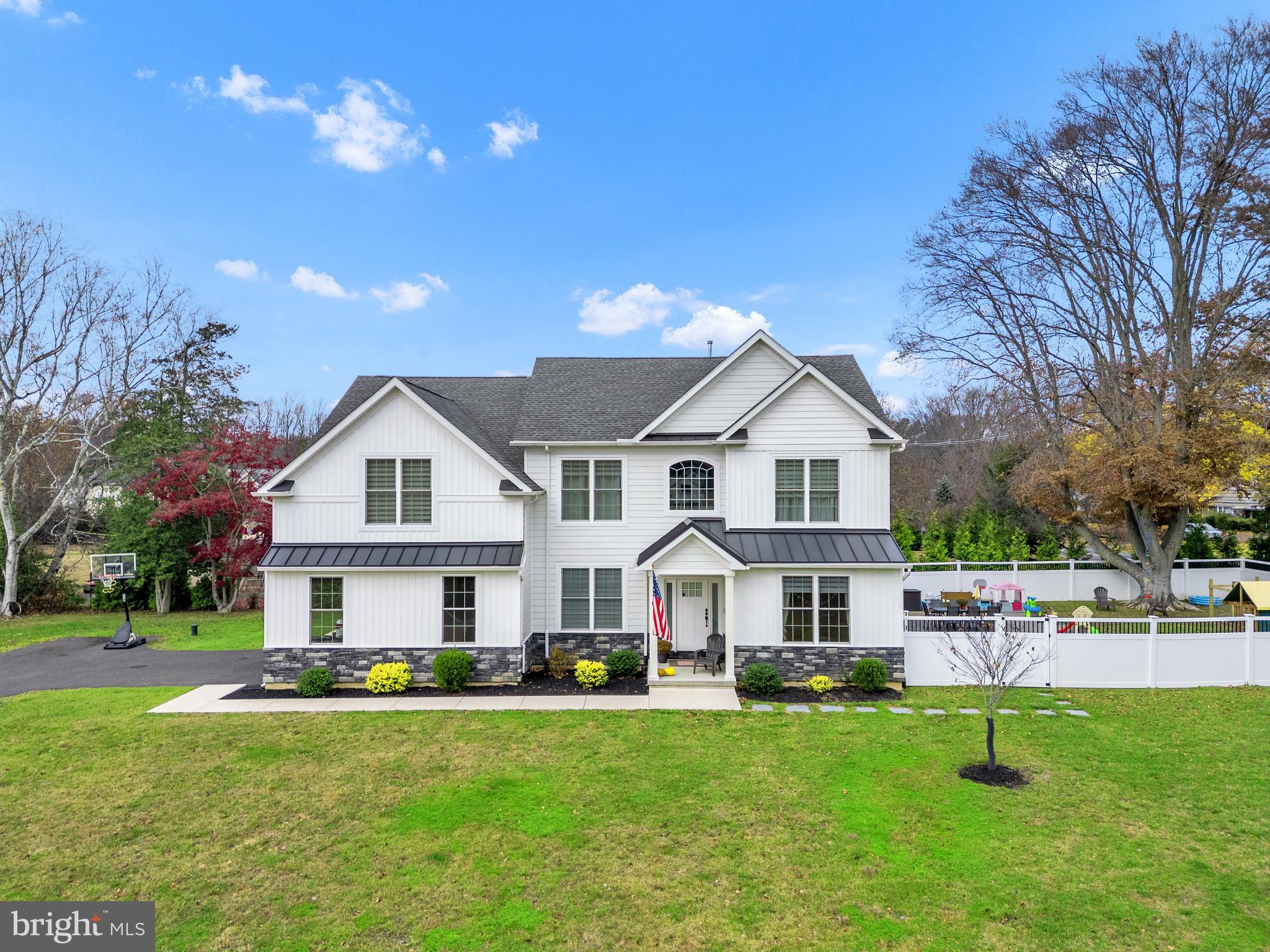 Nestled within the private enclave of the Estates of Bristol Pond, this rare offering highlights a magnificent 5-bedroom, 3.5-bathroom Modern Colonial farmhouse, presenting a lifestyle of sophistication, comfort, and wellness. With a fully finished basement, wrap-around Trex deck, and a striking white façade accented by black metal roofing, this residence radiates curb appeal and timeless design. From the moment you arrive, you’ll notice the attention to detail — from the generous driveway to the towering two-story foyer adorned with Bruce hardwood floors and matte black hardware. To your right, a gracious living room welcomes guests; to your left, a formal dining room with a tray ceiling sets the stage for elegant gatherings. At the heart of the home lies a chef’s kitchen featuring 42” custom wooden cabinetry, white quartz countertops, an oversized dual-waterfall island, Samsung stainless smart appliances, vented hood, recessed microwave, and under-cabinet lighting, all complemented by matte black fixtures. The kitchen opens to a sunlit breakfast area and a spacious family room with a gas fireplace and large windows that fill the space with natural light. A private study, powder room, and a convenient laundry area with Au Pair side entry complete the main level. A floating solid-oak open-riser staircase with sleek black spindles leads to the second floor, where you’ll find an expansive loft area and a luxurious owner’s suite behind French doors. The suite boasts a sitting area with multiple closets, pond views, and a spa-like bathroom tiled floor to ceiling, featuring a floating European vanity, freestanding soaking tub, glass shower with bench, and Grohe fixtures. Three additional bedrooms offer ample space, each with ceiling fans and generous closets. The finished lower level provides endless possibilities, complete with guest quarters, a full bath, and an egress window. Adding to its appeal, this level includes a fitness area, private sauna, and even a podcast recording studio, transforming the home into a true wellness sanctuary. Beyond its elegant design, the home is thoughtfully equipped for modern living: multiple heating zones, tankless hot water heater, energy-efficient Jeld-Wen windows, Therma-Tru doors, a Generac standby generator, and a whole-home water filtration system. Outside, the lavish backyard features extensive hardscaping, a gazebo, vegetable garden, and full perimeter fencing, creating an idyllic private retreat. Ideally located just minutes from Richboro and Newtown, with easy access to major transportation routes, as well as the Churchville Nature Center, Tamanend Park, and the new Rails to Trails Park, this is more than a home — it’s a lifestyle centered on family, productivity, and wellness.