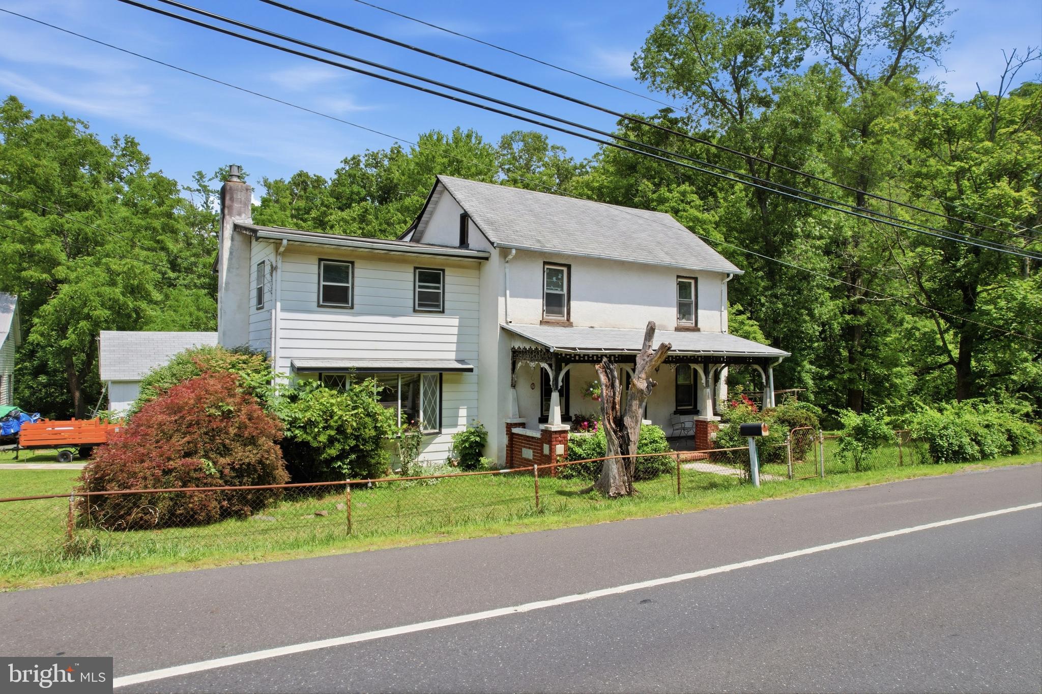 The first floor layout has a large eat-in kitchen; dining room; main level bedroom; and spacious family room with gas fireplace and sliders to deck.  There is an unfinished room off the kitchen that could easily be finished into a mud room/laundry room.  On the second floor, there are four rooms and two full bathrooms.  One stand-alone bedroom offers access to the walk-up attic; a second room with a smaller attached room that could be offices, sitting room or walk-in closet; and accessed through this second room is the primary bedroom with a full bath.  The home has a cozy front porch as well as a large rear deck, and both decking and railings are constructed of maintenance-free materials.  Driveway is large enough for a few cars.  Looking for space for a workshop or storage?  There is a two-story barn here plus an additional outbuilding and a shed.  Do you enjoy the outdoors?  Lake Nockamixon State Park (7 miles away) and Lake Towhee County Park (6 miles away) both offer a plethora of year-round, outdoor recreational opportunities.  Please note that the home needs updating throughout and is being sold “as is”, i.e., buyers are welcome to do their own inspections but sellers will make no repairs and will offer no credits in lieu of repairs.