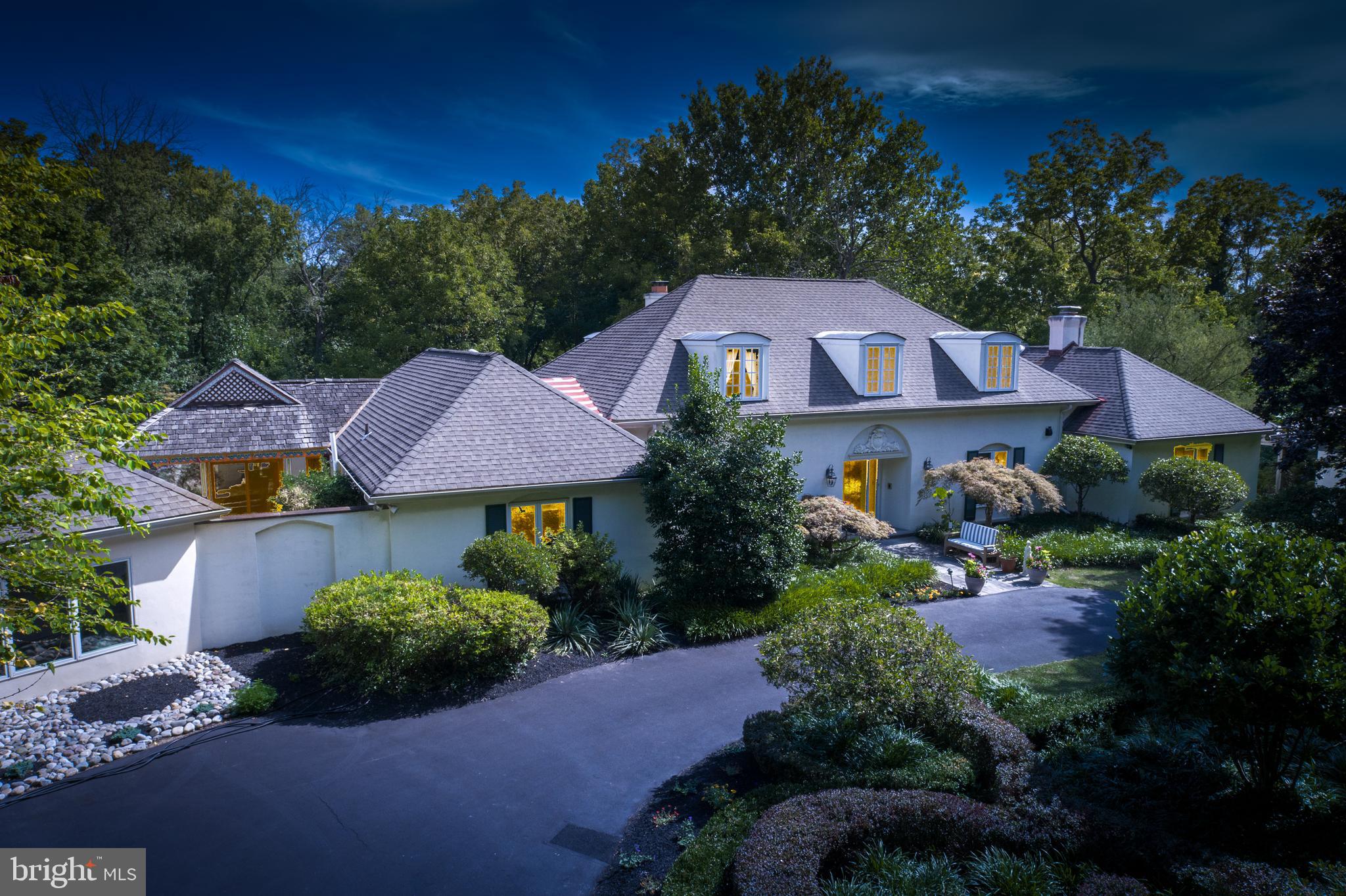 Attention to exquisite detail, and designed with a focus on timeless luxury, this breathtaking home sits on a picturesque 3 acre lot.  Admire the views of the well manicured English Garden, and the beauty of the secluded grounds from the spectacular multi-tiered flagstone terrace that is perfect for all your endless entertaining and outdoor dining needs. The front entrance  greats you with a welcoming foyer, graced with hardwood floors that lead to a one-of-a-kind library, featuring a marble fireplace with a flagstone hearth, and architectural design on the ceiling. The gourmet kitchen includes double islands with intricate mosaic detailing, ample custom cabinetry, marble countertops, custom tile, cherry floors, and a vaulted ceiling with cove lighting, accompanied with a Sub-Zero refrigerator and  high end Wolf appliances.  The stunning millwork throughout this home is nothing less than extraordinary and breathtaking.  The formal dining room displays accommodations for the perfect dinner party, holiday gatherings or enjoying the  evening with cocktails.  Entertaining can also be hosted in the classic formal living room offering two seating areas that are encircled by windows providing plentiful natural light and glistening views of the lush gardens.  The great room boast of  sophistication, and would be considered the centerpiece of this home, featuring custom built-in cherry bookcases spanning the length of the room. The endless views continue in the seven-sided office, with its peaked ceiling and access to the flagstone patio. The  first floor master suite is filled with luxury, attached master bath relaxing oasis that includes a spa-like atmosphere with a steam shower, soaking tub, heated Riverstone floors, and the intimate  landscaping of the private Zen Garden with tranquil fountain.   The master suite bedroom displays silk whisper walls, and offers two generously-sized dressing rooms with custom drawers and closets.  Two bedrooms sit on the second floor with a Jack-and-Jill bath,  and a study alcove that could be used for multiple uses . The finished lower level includes a recreational area, game area, wet bar, caterers kitchen, and a striking 10-seat tiered home theater, along with additional space that would be perfect for an au pair or in-law-suite. The newly renovated one bedroom, one and a half bath guest house is an open design concept, surrounded by windows, providing a  retreat for visiting friends and family. The property features five zones for cooling and heating,  an exceptional sound system throughout the property (inside and out), and  a heated detached 3-car garage. Set against a quiet tree-lined street, this gorgeous residence provides a serene expression poised with grace. Located in a highly rated school district, with easy access to shopping, dining, and entertainment in Chestnut Hill, Ambler, and Philadelphia. Don't miss the opportunity to make this rare find the place you call home - schedule your private tour today.