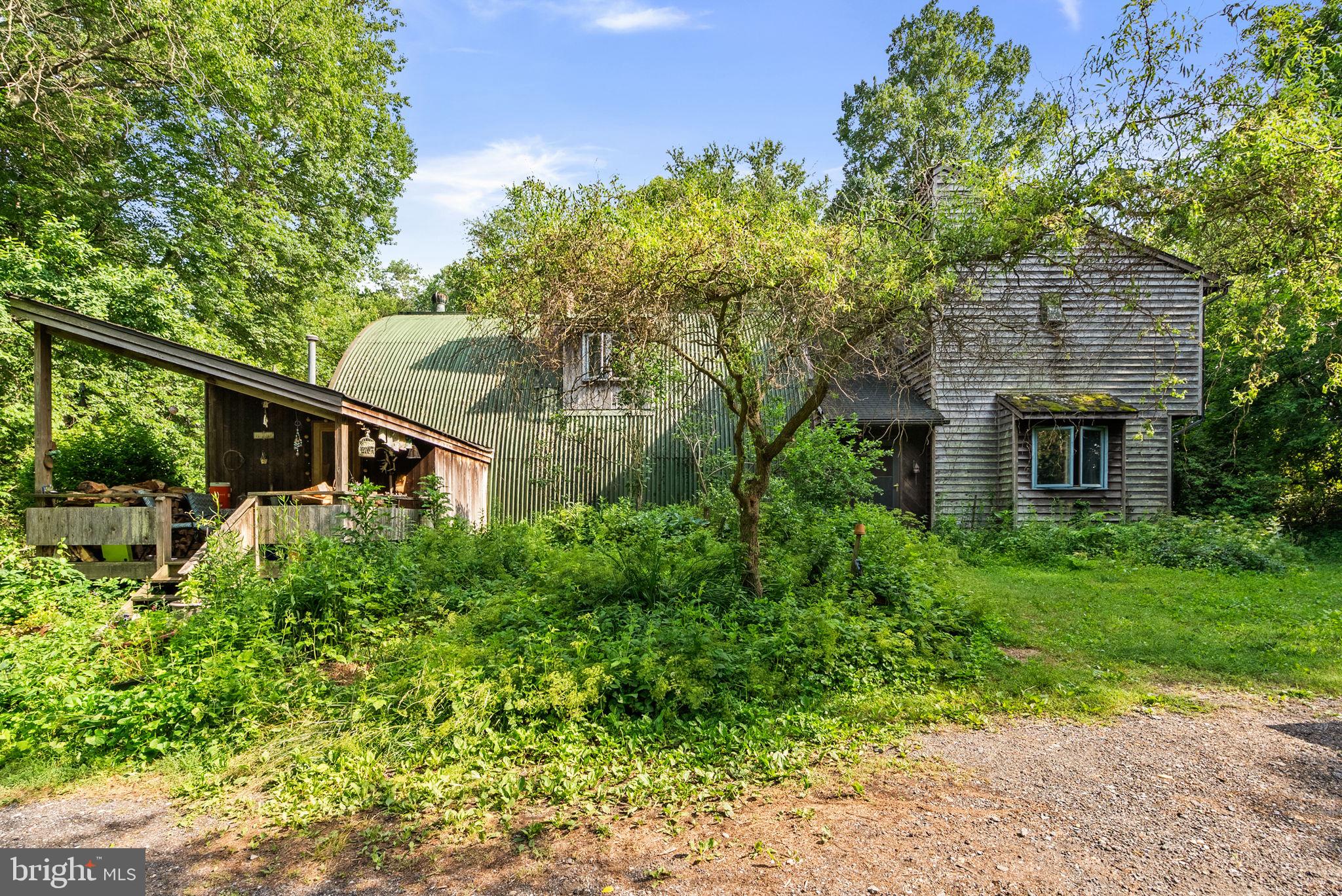Discover a one-of-a-kind 3-bedroom, 2.5-bath home nestled on a serene wooded lot in highly desirable Howard County. Designed for those who appreciate nature, sustainability, and distinctive craftsmanship, this custom-built property offers a truly special living experience.

Step inside to an inviting open floor plan filled with natural light. The bright living room flows seamlessly into the dining area and spacious family room, creating the perfect setting for both everyday living and entertaining. The gourmet kitchen is a chef’s dream, featuring expansive counter space, abundant cabinetry, sun-filled windows and even a charming wood-burning pizza oven.

One of the home's most remarkable features is its passive solar tower heating systtem, visible from the kitchen and adding to the property's eco-conscious appeal.  Just beyond, you'll find a greenhouse—ideal for year-round gardening and embracing a more self-sufficient lifestyle.  Cooling is enhanced with underground cooling tubes!

Upstairs, the cozy primary suite offers a relaxing retreat with a separate shower and a classic clawfoot soaking tub. Two additional bedrooms and a full bath provide comfortable accommodations for family or guests.

The basement offers plenty of storage space, while a detached workshop provides endless possibilities for hobbies, projects, or additional workspace.

This 3+ acre lot features tons of opportunity.  From the mature herb gardens, to the dense woods, this property allows nature to work with you.  Property abuts to Cattail Creek!  

If you've dreamed of a peaceful setting that combines modern comfort with off-the-grid potential, this extraordinary property is ready to welcome you home.