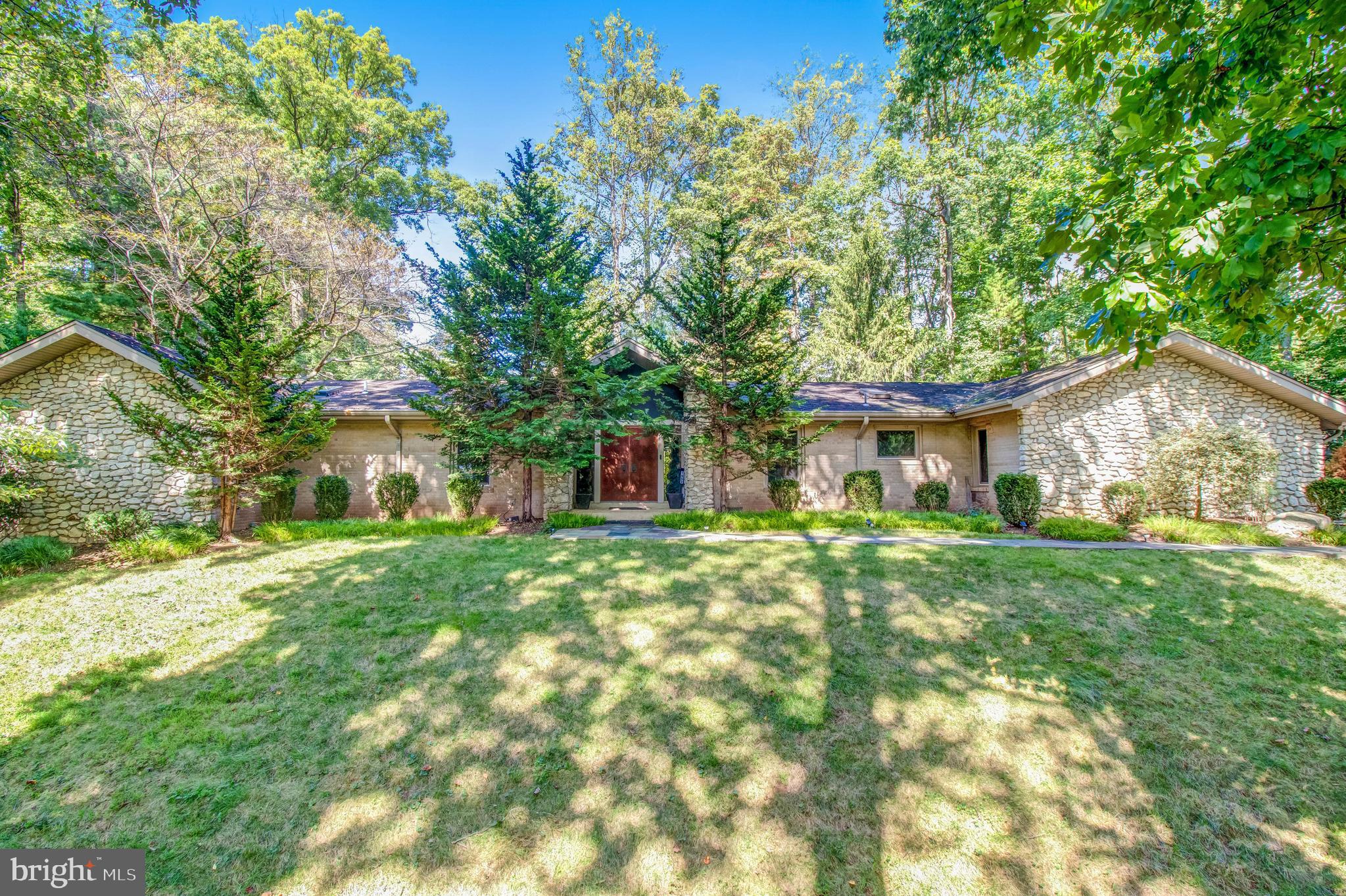 This spectacular stone and brick home on .99-acre in Olde Swinks Mill Estates was custom designed and built by a Swedish architect for his own family.  Enjoy true main level living on a quiet no-thru street where open and light filled spaces blend seamlessly throughout the home and into the park-like outdoor environs.  The main level features a spacious Living Room with a natural stone surround Fireplace, vaulted ceiling, and beautiful views through a large picture window of the small pond and waterfall flowing over natural rock.  The adjacent Dining Room opens via French doors to the back patio for alfresco dining.  The Kitchen is fully equipped with a suite of high end appliances, ample cabinetry, granite counters, and pantry storage as well as an eat-in Breakfast area and direct and convenient access to the Garage.  The large Family Room with 11ft ceilings is a relaxing escape for starting the day with morning coffee or unwinding with a great book by the cozy Fireplace.  With views overlooking the backyard through a large window, custom built cabinetry and shelving, and a gas Fireplace, the Office is the ideal for work-from-home space and can double as a Bedroom. The Primary Bedroom Suite is a luxurious retreat with multiple wardrobe closets and access via sliding door to the back patio, heated pool, and hot tub.  The renovated Primary Bathroom is custom designed with marble tile, double sink vanity, oversized free standing tub, and large steam shower with seamless glass door, bench, and rain shower head.  The space also features an enclosed closet with full size stackable Washer and Dryer for ease and convenience.  Bedroom 2 has a renovated ensuite Bathroom with black and white marble tile embedded with Orthoceras fossils and a seamless glass door shower with rain shower and separate hand shower.  With side above ground windows and walk-out access, the large and open lower level features a spacious Rec Room with gas Fireplace and wood floors, a 4th Bedroom, and renovated Full Bathroom with tub and shower.  A massive Utility Room provides ample storage space.  The oversized main level 2-car Garage is outfitted with storage shelving and a built-in workbench with vise.  The private backyard sanctuary offers an enchanting setting, displaying both natural and landscaped elements at every turn.  A custom built brick wall with artistic lights completely encloses the backyard that features a sparkling heated pool and hot tub, flowing water feature, hardscaping and landscaping, mature plantings, and specimen trees.  The house sits back from the road for privacy and quiet enjoyment. The property comes alive in the spring with flowering trees and bushes and a shady canopy all summer long.  Public water and sewer and whole house water filtration.  This home is an inviting and captivating retreat in one of McLean’s most beautiful neighborhoods and so close to  convenient and happening places such as Tysons, the Silver Line Metro, Reston, Dulles Airport, National Airport, Great Falls National Park, Wolf Trap, I-495 access, and the GW Parkway. Langley High School pyramid.
