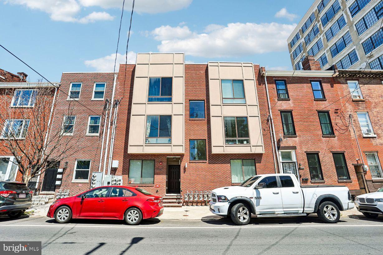 Welcome to this custom-tailored bi-level, 2-bedroom condo in the heart of booming Olde Kensington, offering the rare convenience of two dedicated off-street parking spaces with direct access to the home. Built in 2016, this thoughtfully designed residence showcases an open-concept floor plan with soaring ceilings, gleaming hardwood floors, and abundant natural light pouring through oversized windows that frame picturesque park views. The spacious main living area seamlessly flows into the chef’s kitchen, featuring custom cabinetry, upgraded GE appliances, and a built-in Keurig system—perfect for effortless mornings and entertaining alike. A conveniently tucked-away stackable washer and dryer complete the main level. Downstairs, you'll find two generously sized bedrooms, each boasting oversized windows and custom closet shelving for optimal storage and organization. The bedrooms share a beautiful modern hall bath featuring a glass-enclosed walk-in shower with a built-in bench for a spa-like experience. Residents enjoy access to two exceptional community spaces, including a spacious ground-level patio and an expansive rooftop deck offering sweeping city views—ideal for relaxing, socializing, or taking in the skyline. Parking is never a concern with a large dedicated off-street space that can fit two cars, a true luxury in the city. Situated just blocks from neighborhood favorites including Helm, Stateside Vodka, and local dog parks, this home places you in the center of one of Philadelphia’s most exciting and rapidly growing communities. This is more than a condo—it's a lifestyle upgrade. Mortgage savings may be available for buyers of this listing.