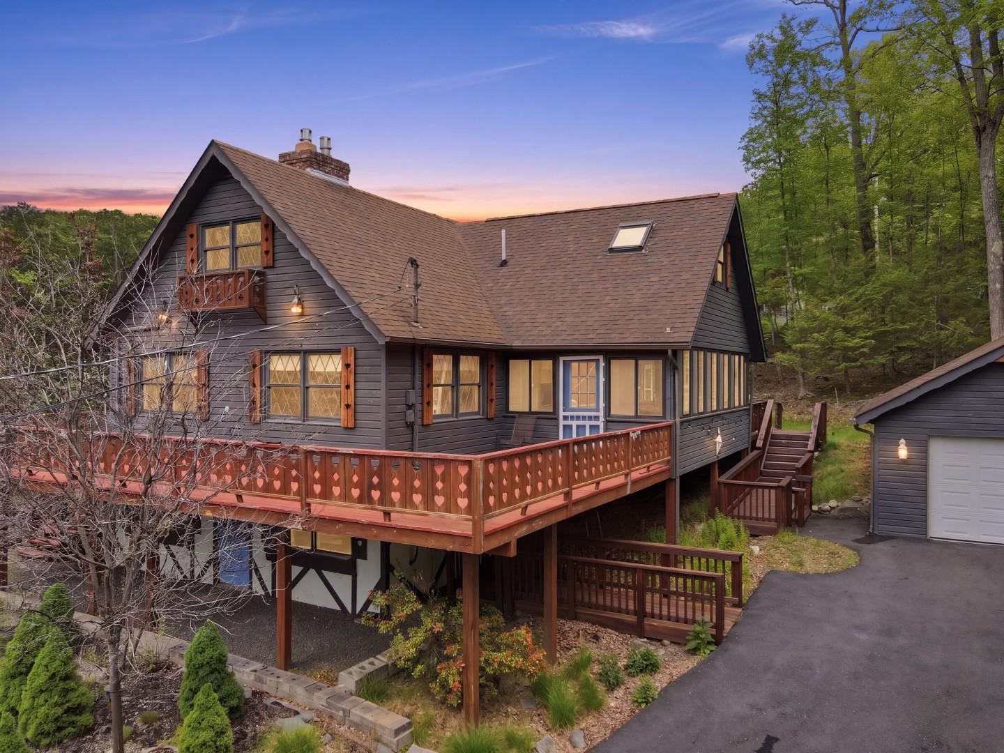 A massive floor-to-ceiling brick fireplace, rumored to contain at least 3,000 bricks, anchors this Swiss-style chalet as it runs through the center of the home to warm both the main living area & finished family room below. Modern propane inserts give you all the ambiance of a traditional fire without the hassle of wood. Built in 1980 in Tanglwood Lakes, this 4-bedroom, 3-bath mountain lake house features warm wood floors and a wall of windows that provide the main living and dining area with natural light. The galley kitchen has granite countertops and a lot of workspace! The main-floor primary bedroom is a relaxing space w/ its own private balcony. Also on the main floor: full bath, laundry hookup, & bedroom that opens directly onto a beautiful screened porch overlooking the backyard. (This versatilebedroom could easily transition into a home office or den depending on your needs).A heated sunroom extends off the living room and can be used year-round. The upper level offers 2 more bedrooms, full bath, a spacious open loft, and a nearly finished bonus room. Downstairs, the finished lower level holds a family room featuring the remainder of that impressive fireplace, a full bath with a soaking tub and separate shower, a laundry area, and a flexible workshop or storage room. Practical aspects include an attached golf cart garage, a detached two-car garage, & a paved driveway. Move outdoors onto the extensive deck, perfect for outdoor entertaining. Enjoy excellent community amenities, including a beach, picnic area, and boat launch on Lake Wallenpaupack, plus fishing and paddling on Lake Tanglwood (no gas motors on Lake Tanglwood) just ⅓ mile away, as well as Paupack Hills golf course. There's a clubhouse & fitness center, too. Beyond Tanglwood Lakes, you are within a short drive of hiking & fishing at Promised Land State Park, skiing at Ski Big Bear, Camelback, Jack Frost/Big Boulder, or Elk Mountain. Go shopping & out to eat nearby, too. Info is deemed accurate but should be independently verified.