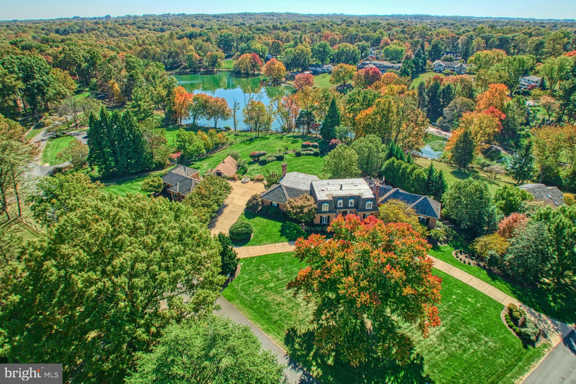Truly spectacular and private  estate in the equestrian neighborhood of  Fox Lake. Sited on 2+ acres overlooking a spring fed lake boasts extensive hardscape, landscaping and an amazing pool & hot tub. Detached 3 car garage perfectly matches the home and the charming barn with potential studio area  has  4 stalls - perfect for this prestigious equestrian community with trails and riding ring.  Meticulous attention to detail & quality throughout will impress  even the most discriminating buyers. Owner completed a $1M+ two level  addition in 2010 including a  main level primary bedroom suite. Enter a hallway  into your private suite  with a charming balcony overlooking the pool,  a wall of built ins and a bathroom with imported Carrera tile. 2 walk in closets and a stackable washer and dryer  complete this spectacular main level addition.  Hardwoods floors on main and upper levels. Soaring coffered ceilings with loads of windows and a fireplace offer plenty of space for relaxing in the great room with doors to huge Azek  deck boasting lake views.  Designer kitchen opens to the great room, perfect for entertaining!   From the Wolf stainless wall oven/microwave and 6 burner cooktop , Sub Zero fridge, 2 dishwashers, European cabinets, tile backsplash, center island and a separate bar area,  the French country feel will make this a favorite place to spend time! Laundry room with pantry and plenty of cabinets off the kitchen with exit to the garage. Cozy study with beamed ceilings, stone surround FP and built ins. Sun filled office with pocket doors for privacy overlooks the pool. Spacious formal dining room and living room with gas FP complete the main level.  The upper level offers a 2nd  primary bedroom with 2 walk in closets and stunning bathroom with separate vanities, walk in shower with multiple shower heads & coffered ceiling. Enjoy lake views from the soaking tub! Bedroom 3 with en suite bath and Bedrooms 4 & 5 share a bathroom.  The walk out lower level addition is every entertainer's dream with a bar overlooking the pool and separate His & Hers changing area bathrooms. A large recreation room with fireplace & built ins, a gaming/office area (this could be enclosed for BR #6)  plus a bathroom and storage room complete the lower level.  Huge unfinished storage room by pool is part of the lower level addition,  Step outside to the breathtaking grounds featuring a pool and hot tub with large Travertine patio and built in grill.  Enjoy the lovely  fountain imported from France next to the brick detached 3 car garage  Bonus patio off the stairs down to barn with 4  stalls and storage area in top of the barn. Stroll down to the lake and enjoy leisurely walks on the trails around the spring fed lake. The Fox Lake  community boasts 183 acres and is comprised of 55 homes, including approximately 26 acres of common property with exclusive private access to the lake, skating pond, equestrian riding ring and meadow, as well as walking and horse trails. It is adjacent to 37,000 acres of parkland with direct and private access to the Difficult Run Watershed stream valleys and trails. Check out the aerial tour here! http://tours.skyblue.media/story/474427/u