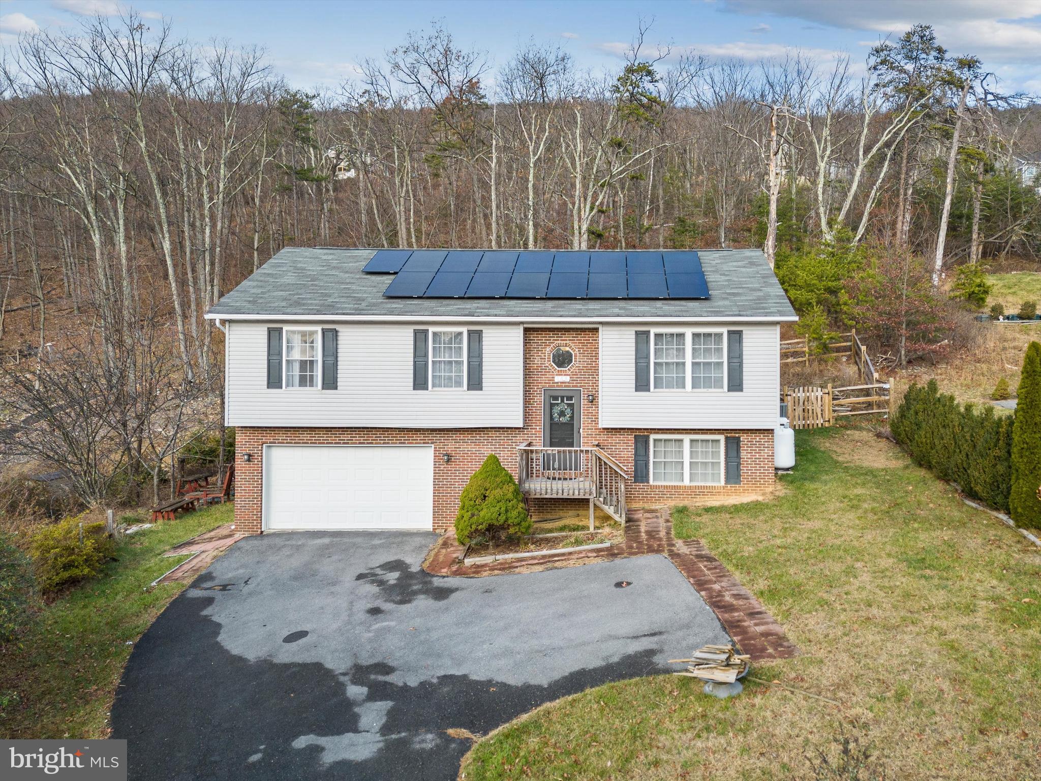 NEW PRICE + Seller will provide a 1-year home warranty with an acceptable offer!! Can you imagine a year-round electric bill that averages less than $35/mo? Want incredible sunrise views? Why not have both! There are no annual fees for solar and this house is carbon-neutral with the solar system in place! You can even sell carbon credits for income - ask me for details! Schedule an appointment to see this well-cared-for home that was quality-built by Warfield Homes. Inside you can warm up to a cozy fireplace in the kitchen/living room/dining area. Or enjoy the magnificent sunrises from the front windows as you take in the excellent views this home has to offer. The owner has taken great care of the home and very recently added a full bathroom on the lower level complete with lovely tile work, new carpet in the bedrooms upstairs, added rear fencing in 2023, installed solar panels in late 2022 that has greatly reduced the cost of electric year-round! SEE DOCUMENT ON WHY CHOOSE SOLAR!! A new HVAC system was installed in 2019 along with a Nest thermostat that conveys. The water heater is less than 4 years old. The washer is less than 5 years old. There is also a water treatment system in place in the basement. In the garage there is a huge workbench/work area and there's still plenty of room to park your vehicle. Enjoy multiple fruit trees in the yard that actually produce. If you're an avid runner, there are several great running trails to enjoy nature at its finest. Of course, Shawneeland offers several playground areas, 2 lakes, and a sandy beach area. Best of all you can enjoy all of this at no charge since there is NO HOA!