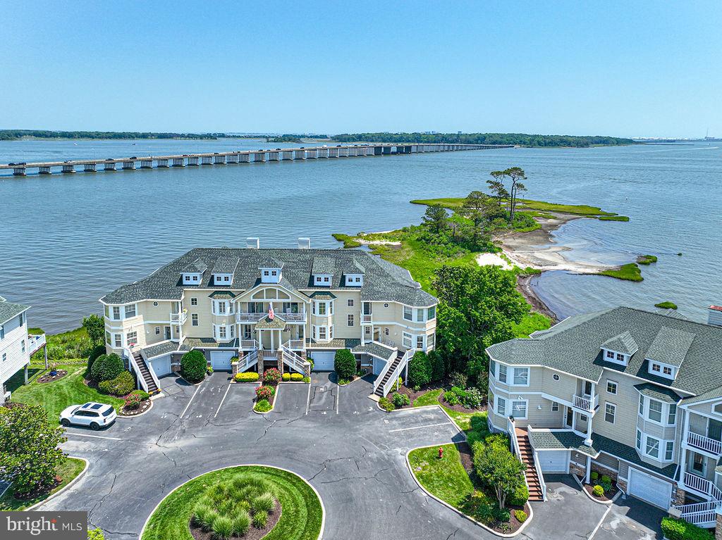 Let the fireworks begin! Welcome to one of Ocean Pines' most spectacular waterfront offerings—a luxurious 4-bedroom, 3-bath direct bayfront townhome nestled within the prestigious gated community of Osprey Point. Perfectly positioned to capture sweeping panoramic bay views, breathtaking sunsets, and the glittering skyline of Ocean City, this exceptional residence offers a front-row seat to the area's most unforgettable waterfront scenery, including holiday fireworks reflected across the bay.From the moment you enter, you'll be captivated by soaring cathedral ceilings, walls of glass framing endless water views, and a stunning floor-to-ceiling fireplace that anchors the light-filled great room. Thoughtfully designed for effortless entertaining, the gourmet kitchen showcases beautifully crafted custom cabinetry, gleaming granite countertops, stainless steel appliances, a spacious breakfast bar, and a butler's pantry for additional storage and preparation space. Adding a distinctive touch of elegance, the dining room features a one-of-a-kind hand-painted artist mural that creates an unforgettable setting for gatherings with family and friends. Outdoor living is simply extraordinary, with three private bayfront balconies inviting you to savor morning coffee, coastal breezes, spectacular sunsets, and evening lights dancing across the water. A retractable awning extends the comfort of the main living balcony, creating the perfect space for waterfront dining and entertaining.The upper-level primary suite is a private sanctuary overlooking the bay, complete with its own waterfront balcony where each evening ends with magnificent sunset views. Spacious guest accommodations ensure family and friends enjoy the same luxurious coastal experience. For boating enthusiasts, the included private deeded Boat Slip #23 with lift is just steps from your door, providing immediate access to the open waters of the bay and beyond. The oversized garage offers exceptional storage for vehicles, paddleboards, fishing gear, bicycles, and all of your coastal lifestyle essentials. Just a short stroll away, the Ocean Pines Yacht Club offers waterfront dining, entertainment, marina amenities, and one of the area's premier social settings. Whether spending the day on the water, relaxing on your balcony, or enjoying nearby Ocean City beaches and attractions, every day feels like a vacation.Offered fully furnished and beautifully appointed, this extraordinary waterfront residence is completely move-in ready. Rarely does a home combine luxury, boating, breathtaking views, and an unmatched coastal lifestyle so effortlessly. This is more than a home—it's a destination where every day begins and ends with the beauty of the bay.