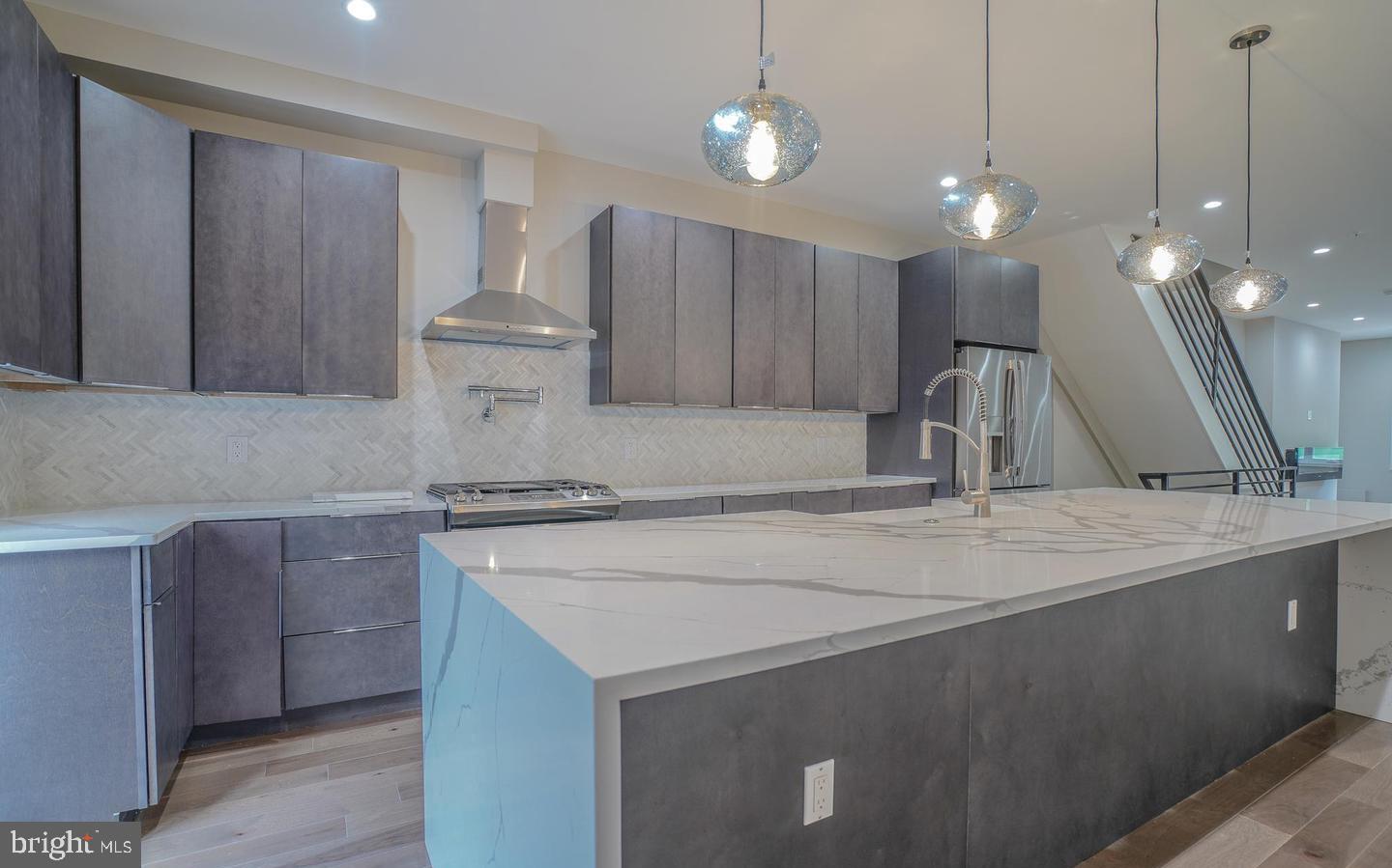 This is a beautiful 99% new construction home located in the 19125 area. It features a modern open floor plan design with light hickory hardwood flooring on the first floor. The living room has a wall-mounted electric fireplace and recessed LED high hats throughout. The living room and dining room are combined into one large space. The huge gourmet island kitchen is stunning with quartz countertops, a waterfall island countertop with bar stool seating, wine fridge, tumble marble backsplash, built-in microwave, stainless steel refrigerator, farmers sink, stainless steel dishwasher, garbage disposal, stainless steel gas range, pot filler, stainless steel range hood, and pendant lights. Sliders lead out to a large maintenance-free cement yard with new pressure-treated fencing. 

The finished basement has ceramic tiled flooring, ceramic tiled large powder room, a utility closet, 200 amp electric panel, gas hot water heater, 2 zone central air and hot air heat, sprinkler system, washer dryer hook up, and recessed lights. Behind closed doors is a sump pit and pump. Second floor offers a large bedroom with hardwood floors, double closet, and a hall bathroom with tiled floors and walls, vanity, and modern lighting. The large front primary bedroom has a walk-in closet area and a full bath with double sink and stall shower with beautiful glass doors.

On the third floor, there is a second front primary bedroom with a walk-in closet, a huge full bath with soaking tub, shower with glass doors, tiled, double sink, and LED vanity. Fourth bedroom is also located on the 3rd floor. Stairs to the 4th floor leads to the roof deck with beautiful skyline views and plenty of room for your patio/roof furniture.

This large house has dual primary bedrooms and 3.5 baths. Only half the original foundation was used in this building; everything else is brand new. Lot behind is being developed soon. Contact the lister for more details. Your buyers will not be disappointed!