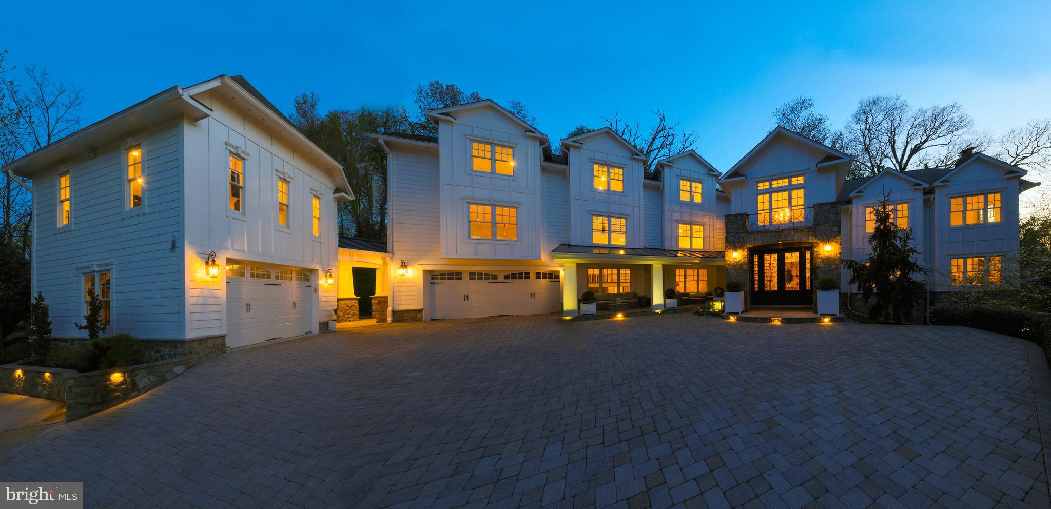 This gorgeous estate in the heart of McLean offers nearly 9,000 sq ft of luxury with 8 bedrooms, 7.5 bathrooms, 2 double garages, an oasis-like back yard with over $250K worth of upgrades, a transferable membership to the highly sought after Highlands Swim and Tennis Club just 0.5 mile away, (currently a waitlist)  and 0.2 miles away from Linway Terrace Park featuring multiple sports fields. The backyard features a large custom design limestone & blue stone patio that can be enjoyed during all seasons of the year. Relax in the heated jacuzzi to the sound of the waterfall, surrounded by mature evergreens, and walk bare feet on the limestones that never heat up in the sun. The outdoor kitchen is fully equipped with a stone pizza oven, gas cooker, gas grill, sink and granite counters. The large pergola is equipped with a ceiling fan and sound system. Enjoy the firepit during colder months.  The upper end of the backyard is home to a half size basketball court and a shed.
The front yard is equally impressive with a paver driveway, a spacious front porch, and double entry wrought iron door.
Enter to a large, two-story open galley landing. Gleaming hardwood floors run through the entire main level. The kitchen is a chef’s dream! Calcutta gold marble countertops, massive kitchen island, 6 ring Wolf gas range with griddle & double oven, extra double wall oven, Sub Zero refrigerator, Bosh dishwasher, Wolf microwave, wine cooler, tons of cabinet space with pull out drawers, and a room size pantry. From the spacious breakfast area, French doors lead to the fabulous backyard. The formal dining room sets the perfect atmosphere for any occasion. The built-in sound system and ambient lighting provide for an intimate atmosphere. When entertaining, your guests will always be wowed by the 23’ tall, vaulted ceilings in the spacious family room, surrounded by windows on three sides. Notice the marble hearth by the wood burning fireplace and the Jeld Wen insulated windows for serene soundproofing. From the family room go down to the finished walk-out basement in full daylight. A large rec room with fireplace, wet bar with quartz brick façade and mini fridge, full bathroom and large storage area awaits. The main level bedroom and full bathroom are ideal for an in-law suite. The upper-level features hardwood floors on the stairs and in the hallway. The primary bedroom suite is like a sanctuary, projecting calm and peace. It boasts a custom design walk-in closet with a center island and chandelier. Unwind in the spa like bathroom with heated marble floors, freestanding soaking tub, steam shower, quartz brick backsplash around the vanity and a private balcony. There are 4 more very spacious bedrooms on this level, and two full, modern bathrooms with double vanities. Two of the bedrooms have vaulted ceilings, and two of the bedrooms share a Jack and Jill bathroom, accessed through large walk-in closets. An awesome loft area over the primary bedroom suite is the perfect living space for teens and young adults. With a large entertaining area surrounded by windows, a study, a spacious bedroom and a full bath with jacuzzi tub, life doesn’t get better than this! A spacious landing makes life easy as you enter the home from the attached garage. This space is outfitted with built-in units for coats & shoes, allowing you to keep the main entrance of the home always tidy. From this space, another door leads to the backyard and patio. Follow the covered breezeway from the attached garage to the detached garage. The upper level of this building features a large bedroom with hardwood floors, and a full bathroom, creating an ideal space for house guests. The entire home has been recently painted, and all carpets are newer. Insulated windows and doors, sprayed foam insulation on the roof deck and basement walls, top of the line Carrier Infinity 7 zone HVAC system, and many more high-end finishes will wow you!