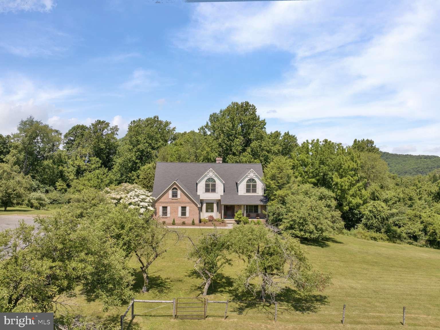 Perched atop a hill with views that stretch for miles, this brick residence captures equally stunning sunrises and sunsets—a private vantage point where timeless craftsmanship meets modern luxury. 7,000+ square feet of living space, fully renovated in 2026, sits on almost 12 acres of rolling lawns, mature landscaping, and a historic stone barn, all reached by a picturesque apple tree-lined drive.
The 2026 renovation runs top to bottom: a reimagined kitchen with quartz countertops, updated baths, a new roof, and new garage doors mean the heavy lifting is done. Built in 1990 and thoughtfully brought into the present, the home pairs solid brick construction with fresh, modern finishes. Inside, an exceptional floor plan flexes effortlessly between quiet everyday living and grand-scale entertaining—expansive rooms, custom details, and walls of windows that fill the space with natural light and frame those sweeping countryside views from every angle.

Outside is just as compelling. The all-original stone barn anchors the entrance—a striking historic landmark with endless possibility, whether as a workshop, studio, collector’s space, or your own next vision. Beyond it, open acreage and mature apple trees give way to nearly five acres of private woodland laced with your own walking trails—a rare retreat for morning hikes, quiet afternoons, or simply space that’s entirely yours. Panoramic hilltop views and a true country lifestyle round out the setting, with shopping, dining, and major commuter routes still within easy reach.

A luxury family estate or a private sanctuary with room to breathe—this property is both. Estates of this caliber rarely come to market. Schedule your private tour.