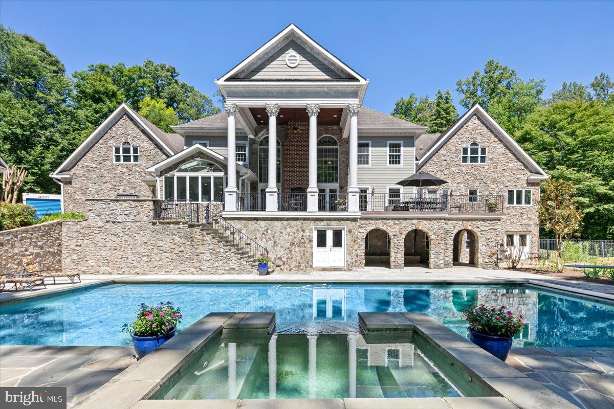 Welcome to Greek Revival architecture, a custom home designed and built by the owner, a professional engineer and architect.   A rare offering in desirable Balmoral Greens neighborhood, offering refined entertaining and everyday luxury.   Nestled at the end of a quiet cul-de-sac, this extraordinary estate offers 12,000 square feet, a four-car attached garage and a two-car detached carriage house with unfinished apartment space above the garage, on 2.4 private acres backing to protected parkland.
The stately home features 6 spacious bedrooms, 7 full baths, and 2 half baths, including a luxurious main-level primary suite and a second upper-level primary suite ideal for multigenerational living.   Soaring ceilings, exquisite millwork, and sophisticated architectural details define the interiors, highlighted by dramatic stairs, the two-story family room with coffered, ornate ceilings and walls of windows overlooking the grounds.
The lower level boasts a beautiful large bar area with wine cellar, a sitting area that leads to the game room, a theater with bi-level seating for eight, an office, an exercise room with adjacent unfinished space perfect for a sauna as well as direct access to a full bath, and a bright spacious room with walls of windows, perfect for a wellness retreat or yoga studio. 
Designed to inspire, the home also offers expansive unfinished attic spaces on both sides of the residence with high ceilings—an exceptional opportunity to create additional bedrooms, offices, or any custom space envisioned by the next owner.
Outdoor living and entertaining at its best, featuring a grand covered terrace overlooking the oversized pool,  and a charming stone pool house with a full bath, a changing room,  kitchen, and covered patio with a wood burning fireplace overlooking the spa.  All these, surrounded by  beautifully landscaped grounds, the endless parkland with mature trees, with access to the Johnny Moore Creek, located a few yards from the perimeter of the property, creating a private resort-like setting. 
Perfectly positioned within one of Northern Virginia’s most coveted communities, residents enjoy direct access to over 17 miles of scenic trails for hiking, horseback riding, and nature walks, proximity to Westfields Golf Club and the charming town of Clifton which offers acclaimed dining, wine tasting, cafés, boutique shopping and community events.
Offering a rare combination of privacy, natural beauty, and accessibility, this exceptional estate provides a tranquil suburban sanctuary, with convenient access to major routes, including Routes 28, 29, I-66, Braddock Road and Fairfax County Parkway.