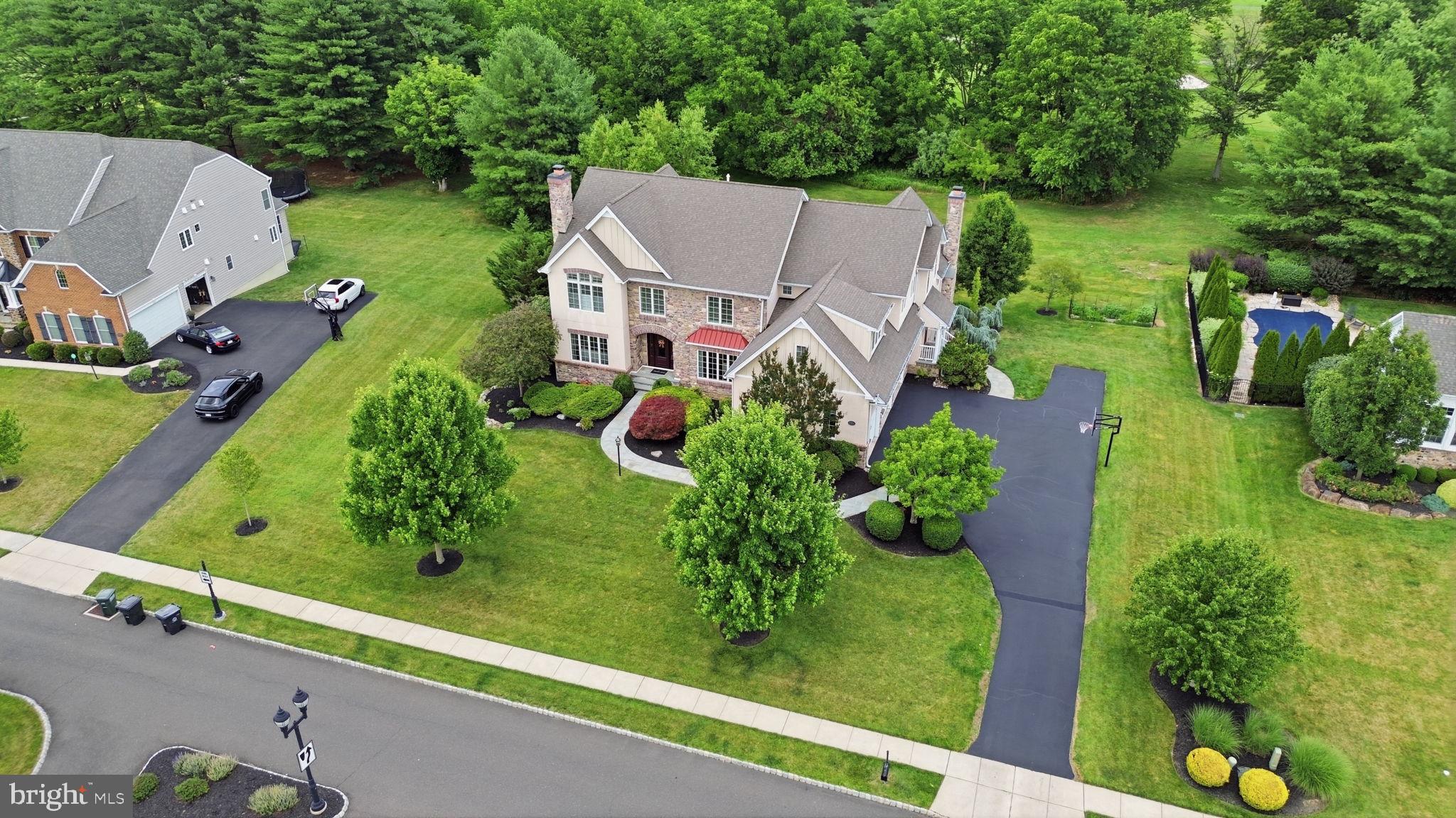 Welcome to 51 Wordsworth Drive, an extraordinary estate nestled within the prestigious gated community of Poet's Walk in Ivyland, situated  in the highly acclaimed Council Rock SD. Offering 5,000 square feet of living space plus an additional 2,000 square feet of beautifully finished lower level. This exceptional 5-bedroom, 3-full, and 3-half-bath residence seamlessly combines timeless elegance with luxurious modern upgrades. Poised gracefully on the fairway of the 13th hole of Spring Mill Country Club, the property enjoys protected backyard green space through a perpetuity clause, ensuring lasting privacy  for years to come. From the moment you arrive, a freshly sealed driveway leads to the oversized three-car garage, while a winding Bluestone paver walkway guides you past mature, manicured landscaping. The elegant, brand-new front door creates an unforgettable first impression, opening into a grand two-story foyer where soaring ceilings, exquisite millwork, and refined finishes set a sophisticated tone. To the right, the formal dining room showcases elegant wainscoting and a large bay window that floods the space with natural light. To the left, the formal living room is surrounded by windows and anchored by a cozy gas fireplace with a classic marble hearth. Just beyond, is a private  office featuring  double-door entrances, several oversized windows overlooking the yard.  The heart of the home is the spectacular chef's kitchen, thoughtfully updated for everyday living and grand-scale entertaining. Premium appointments include a Sub-Zero refrigerator, an impressive 8-burner Wolf range with double ovens, a warming drawer, two walk-in pantries, granite countertops, a stylish subway tile backsplash, and a designer tile feature. A spacious central island offers additional prep area and a perfect gathering spot for family time. A beautifully appointed wet/dry bar with sink seamlessly connects the kitchen and dining room, while the spacious breakfast room opens through sliding doors to the rear deck, offering panoramic views. Flowing effortlessly from the kitchen is the breathtaking family room, highlighted by soaring coffered cathedral ceilings, a custom gas fireplace with a designer tile surround and reclaimed railroad tie mantle, motorized custom blinds, and new carpeting. Two conveniently located powder rooms, a side entrance with a welcoming foyer and walk-in closet, and a rear staircase complete the main level.  Ascend the stunning main staircase—featuring custom wainscoting and a charming built-in reading nook on the landing—to reach the impressive, gallery-like upper hallway. Enter the luxurious primary suite, a true private retreat offering hardwood flooring, a tray ceiling, plantation shutters, a spacious sitting room, and two custom walk-in closets. The completely renovated, spa-inspired bath features heated floors, a steam shower, a soaking tub, dual Restoration Hardware vanities, and floor-to-ceiling tile. Bedrooms two & three each offer ceiling fans and walk-in closets while sharing a thoughtfully designed Jack-and-Jill bath with individual vanity areas. Bedrooms four and five share a second Jack-and-Jill bathroom. Bedroom four is generously sized and perfectly suited as a guest room, while bedroom five offers an amazing space for a playroom.  Enjoy an upstairs laundry room w/ built-in cabinetry for everyday convenience. The sunlit, finished walkout lower level offers endless possibilities for recreation. A custom granite-topped bar with ceramic tile flooring, a sink, a dishwasher, and a refrigerator creates the ultimate entertaining spot. This level also features expansive media areas, a dedicated exercise room with sliding doors leading to the patio, a hobby room, powder room , and also plenty of storage. Updates include full stucco remediation, all new windows, gutters, freshly painted throughout, inground sprinkler system, 2 zones of HVAC. Just minutes to shopping and dining. Schedule your private tour today