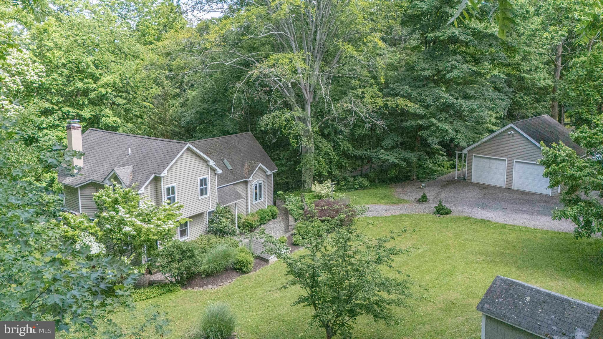 Nestled along a Private  Road and available by appointment, this inviting custom home is set on over 1.6 acres and surrounded by mature trees and lush landscaping. Meander down the stone steps and walkway to a covered front entry framed by beautiful perennials.

Inside, an inviting foyer opens to the cozy living room featuring a wood burning fireplace, and custom window seats —perfect for enjoying a good book while taking in serene woodland views. The bright, open kitchen is appointed with white cabinetry, granite countertops, a natural tile backsplash, stainless steel appliances and a convenient island illuminated by a Hubbardton Forge two-light pendant. 

The adjoining dining area overlooks an expansive Iron Wood hardwood deck tucked among the trees, an ideal setting for relaxing on a summer afternoon or hosting friends for an evening dinner. Down a separate hallway, a main level bedroom with a separate entrance, full hall bath, offers flexibility as a guest retreat or home office.  An open Mahogany staircase leads to the second level, where a spacious bedroom features a vaulted ceiling, custom built-ins, a walk-in closet plus two additional closets, and a wall of windows showcasing treetop views. A well-appointed hall bath with a soaking tub and glass-enclosed shower connects the two bedrooms on this level.

The property also includes an oversized detached two-car garage with a workshop and additional storage space, along with a storage shed for lawn equipment, and a separate shed ready for gardening enthusiasts. 

From this unique home and its bucolic property, enjoy all the area has to offer, from the Delaware River and Towpath to the charming river towns and renowned restaurants of Bucks County, as well as nearby destinations just across the bridge in NJ. With ever-changing scenery, the property offers a stunning backdrop in every season, from lush summer greenery to vibrant fall foliage and peaceful winter views.