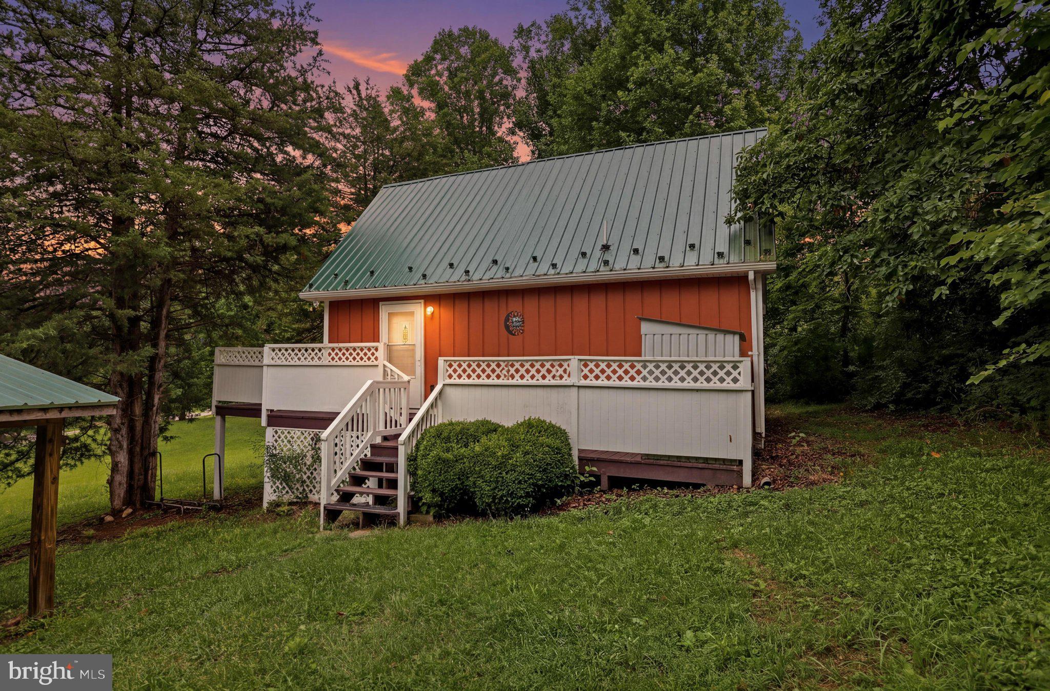 Whether you're searching for a full-time residence, or a weekend retreat this charming chalet-style home offers the perfect blend of comfort and outdoor recreation. On 2.00 mostly cleared acres, the home features an open-concept floor plan with a living and dining area, creating a warm and inviting space for relaxing or entertaining. The full kitchen is equipped with a double sink, refrigerator with ice maker, built-in microwave, and washer and dryer tucked behind double doors. As the seasons change, cozy up beside the wood stove and enjoy the inviting ambiance. The main level includes a comfortable bedroom and a full bath with a new vanity and additional storage. The loft provides endless possibilities as a second sleeping area, home office, game room, or reading nook. Enter through the side entrance onto the wraparound deck—perfect for grilling, outdoor dining, or simply enjoying the peaceful surroundings. A spacious storage shed at the rear of the property offers plenty of room for tools, outdoor gear, or recreational equipment.    Located in the desirable Cacapon River Meadows community, owners enjoy access to a beautiful common area along the sparkling Cacapon River with picnic tables, swings, and opportunities for kayaking, tubing, swimming, and fishing. Conveniently located approximately 7 miles from Route 522 and the historic town of Berkeley Springs, this property offers the perfect balance of privacy, recreation, and easy access to shopping, dining,  concerts in the park and local attractions . Don't miss your opportunity to own this inviting mountain getaway!