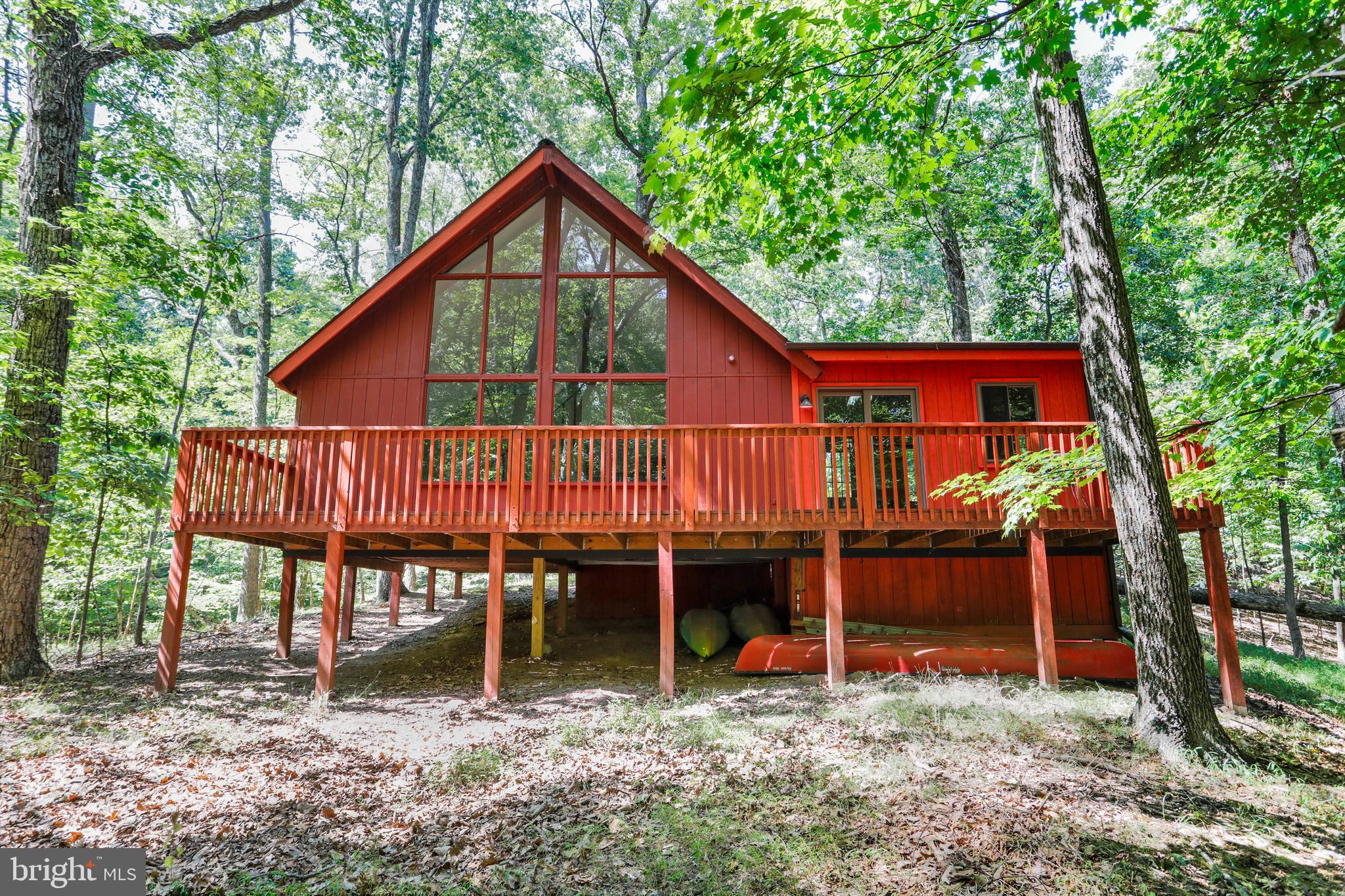 Whispers of the Woods – A Serene A-Frame Hideaway
Tucked at the end of a quiet cul-de-sac on nearly 3 wooded acres, this enchanting A-frame cottage is the retreat you didn’t know you needed—but won’t want to live without. Set beneath a cathedral canopy of trees in The Woods community, the home is embraced by nature on all sides, offering ultimate privacy, peaceful forest views, and even the soothing sound of a babbling brook meandering at the property’s edge.
Step inside and exhale—the light-filled interior welcomes you with soaring ceilings, an open-concept layout, and a dramatic wall of windows in the great room that brings the outside in. Watch the sun filter through the treetops as you sip coffee from the inviting sunroom, or slide open the glass doors and gather on the expansive 38x8 deck—perfect for sharing laughter, stories, and starlit evenings with loved ones.
This cozy cottage features two comfortable bedrooms and one stylishly updated full bath. The kitchen is a dream with updated cabinets, new stainless steel appliances, granite countertops, and recessed lighting that adds warmth and polish to the space.
Offered with a Class B membership (optional, with a $3,150 initiation fee), you’ll have access to all the recreational amenities The Woods has to offer. And for an easy move-in, some furnishings convey—just bring your weekend bag and a bottle of wine.
If you’re longing for a place where time slows down, where privacy is plentiful, and nature sings you to sleep—look no further. Your peaceful escape is waiting.