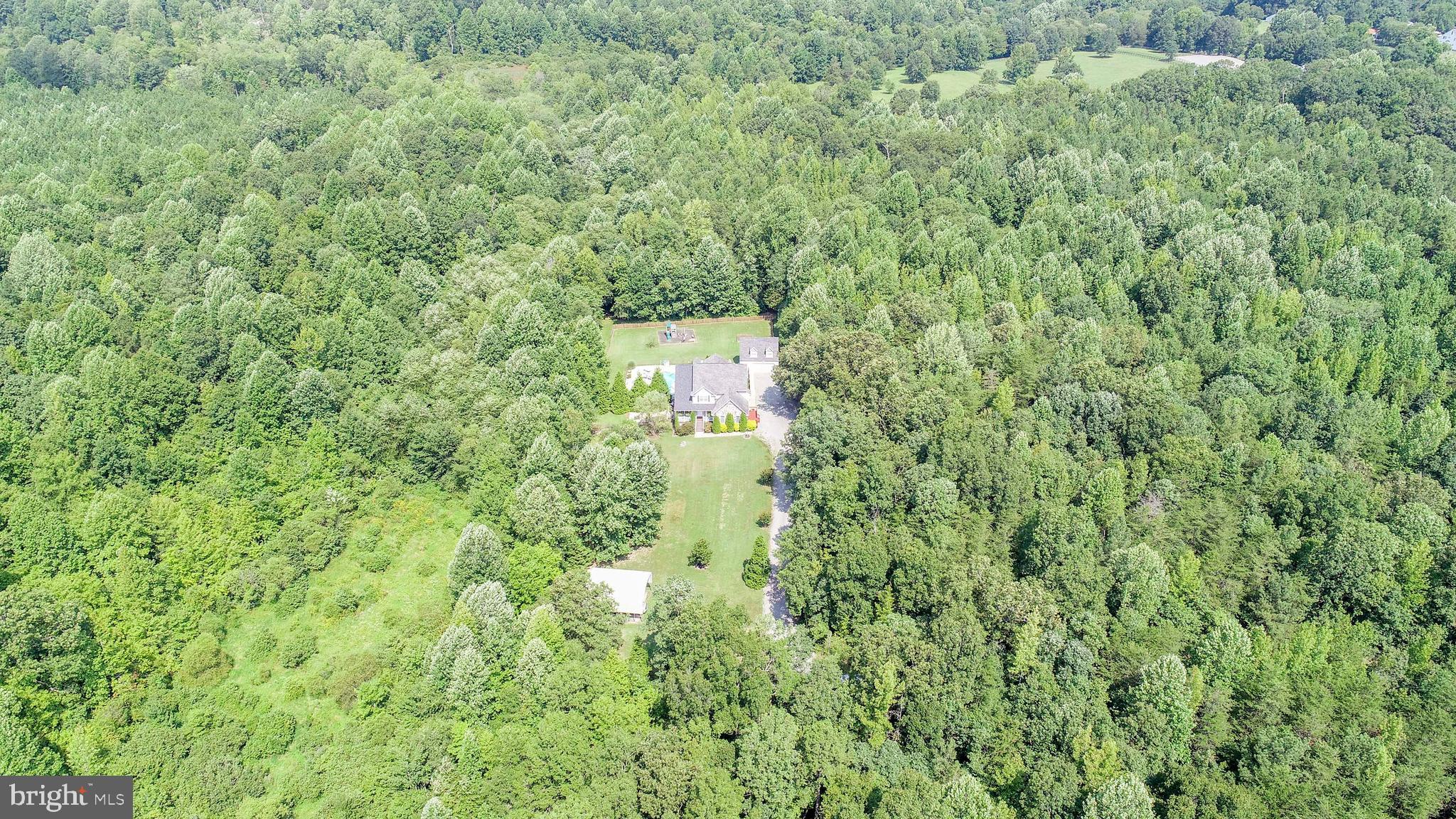 Looking for space and privacy? This beautiful 3 level home offers both w/6 BRs, 4.5 BAs & tucked amongst the trees on almost 15 private acres. The main level consists of a den/sitting room, formal DR w/Tray ceiling & crown molding, gourmet kitchen w/granite counter tops, stainless steel appliances & 2 large pantry areas. Bar top eating area as well as a breakfast table area, Great room w/gas FP & a covered deck overlooking the pool. There is a main level en suite w/FB & private deck. The 2ndlevel offers a 2nd ensuite w/gas FP, FB & a very generous walk in closet (17x6.4), there is an office, laundry room, FB & 2 add'l large BRs on this level, on of which has private access to the screened in porch. The 3rd level offers 2 more BRs & full bath. There are 4 zones in the house,80 gallon hot water heater, intercom system, water treatment system & the house is wired for a generator & 30 am service for RV hookup.. Outside the fun continues w/the inground pool, patio area, play ground, zip line & slack line. Oversized detached garage has full finished upper level, carport w/sep.110 service & add'l 30 amp hookup for RV. Make this home a "must see"!