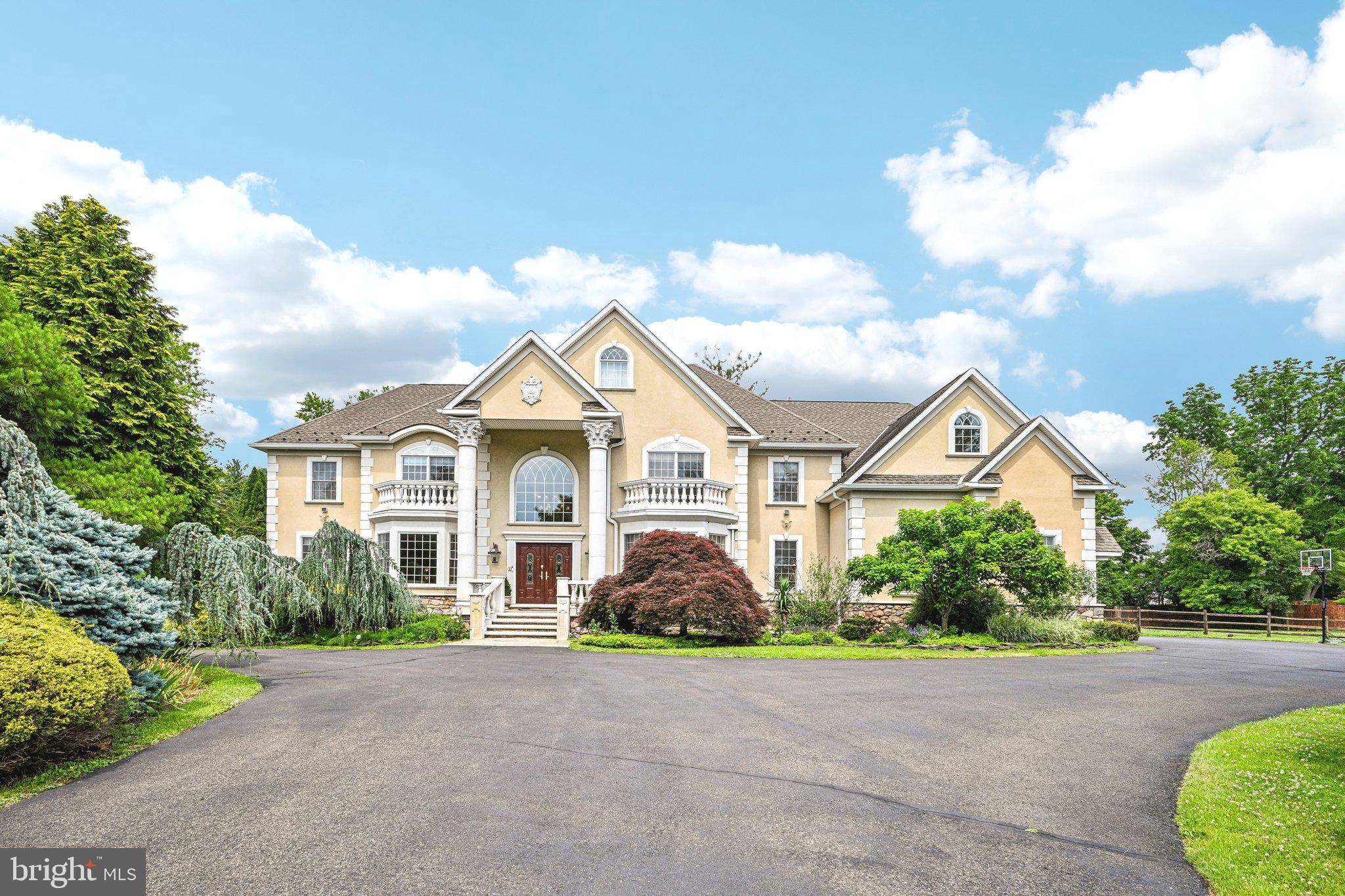 Set at the end of a private road on 1.34 acres, 434 Meetinghouse Road, in sought-after UPPER DUBLIN SCHOOL DISTRICT, presents an exceptional custom estate with approximately 6,900 square feet, four bedrooms, three full baths, two half baths, and an oversized 3-car garage. A sweeping circular driveway, stately columns, and front steps create an elegant sense of arrival.
Inside, the dramatic two-story foyer introduces the home’s refined architecture with a curved staircase accented by wrought-iron details, a hand painted ceiling medallion and imported chandelier with motorized lift. Formal living and dining rooms frame the front of the residence, each enhanced by oversized windows and abundant natural light. The dining room is especially impressive, with custom millwork, chair-rail detailing, a tray ceiling, an ornate chandelier, and views across the front grounds.
The main living spaces are designed for both everyday comfort and gracious entertaining. The family room features a propane fireplace with a mantle and newly installed herringbone wood floors, flowing directly into the gourmet kitchen. Appointed with a Sub-Zero refrigerator, double ovens, a Thermador professional 6-burner cooktop, a large center island with seating and a prep sink, a butler’s pantry, and a walk-in pantry, the kitchen is both beautiful and highly functional. The adjoining dining area is distinguished by vaulted ceilings and large Palladian windows that fill the space with natural light.
Radiant-heated marble floors add warmth and comfort across much of the first level, while six-zone heating, and three-zone cooling provide efficient, customized climate control throughout the home. A private office offers flexibility as a possible fifth bedroom. Nearby, the formal powder room features a distinctive French-inspired vanity, adding a memorable design element. A mudroom, off the garage includes an additional half bath, and storage plus a back staircase from the kitchen offers convenient access to the upper level.
Upstairs, new carpeting and new wood flooring enhance the bedroom spaces. The primary suite is a private retreat with a tray ceiling, two oversized walk-in closets, and a spa-style bath featuring a soaking tub, a large shower, and dual vanities. Bedrooms two and three share a Jack-and-Jill bath, while the fourth bedroom includes a private ensuite bath. Built-in closet systems provide thoughtful storage throughout, and the second-floor laundry room is conveniently located near the bedrooms and could be converted back to another bedroom.
The third-floor bonus room/recreation area offers versatile space for a media room, game room, studio, or private lounge. The basement provides extensive storage, future possibilities for gym, recreation room, and is plumbed for bathrooms should you decide to further finish it. Outdoors, the rear patio creates an inviting setting for dining and entertaining, while the flat side yard offers room for recreation, a play area, gardening, or a future pool.
Ideally located within walking distance to the elementary school, near Route 309, Ambler Borough, shopping, and restaurants, this distinguished residence combines grand scale, custom craftsmanship, and modern comfort in an impressive estate setting. Schedule a private showing to experience the home firsthand.