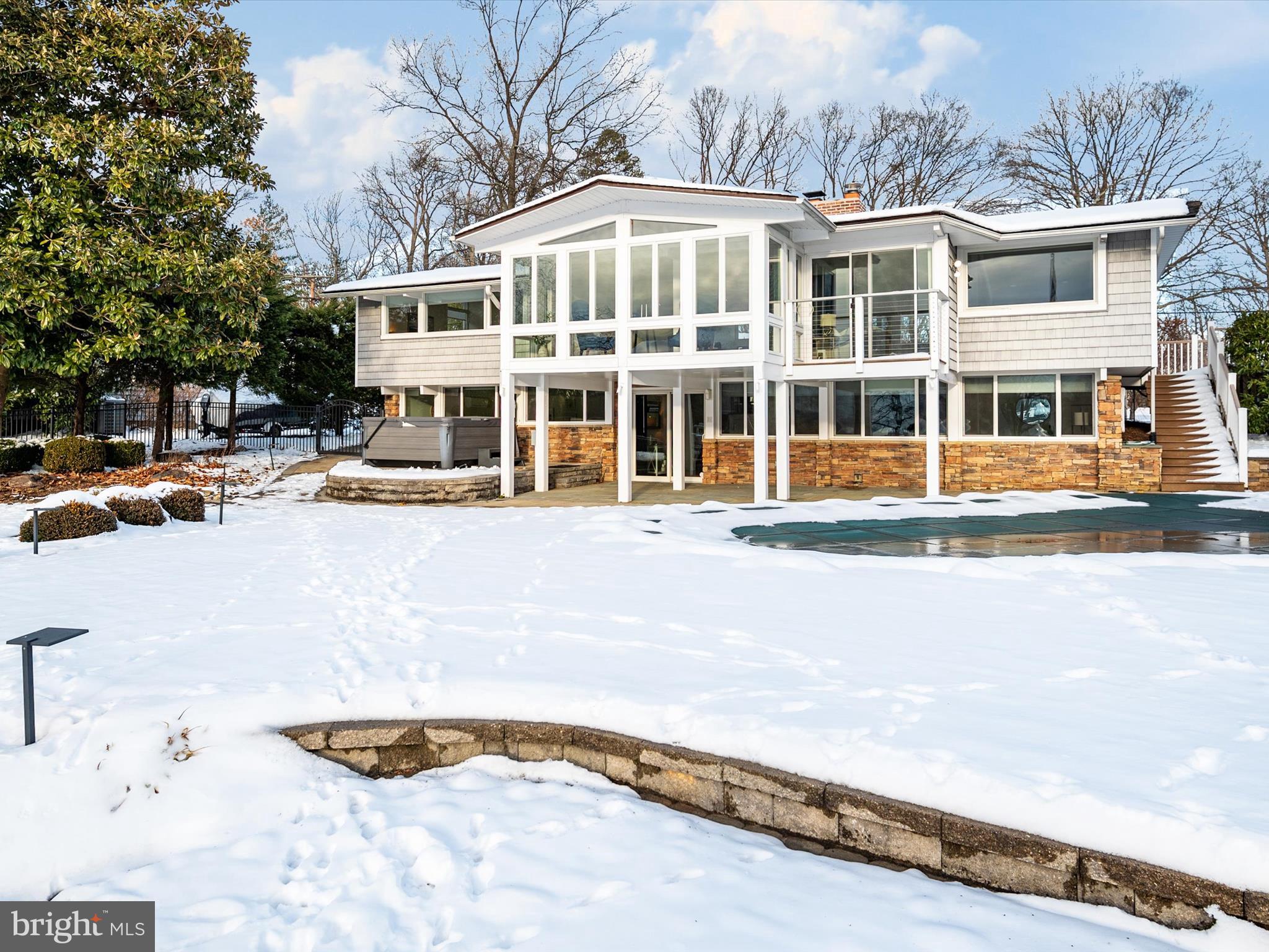 Rare Opportunity to Own a Custom-Designed Waterfront Retreat on the Mouth of the South River! This stunning modern home offers an unparalleled lifestyle with breathtaking water views and spectacular sunsets. The open-concept layout with over 3100 SF showcases soaring cathedral ceilings, gleaming hardwood floors, and expansive floor-to-ceiling windows that flood the home with natural light. The state-of-the-art kitchen, fully redesigned in 2021, features Quartz countertops, sleek cabinetry, and professional series appliances, making it an entertainer's dream. The living room offers panoramic water views, a wood-burning fireplace, and seamless access to a sun deck overlooking the sprawling backyard and waterside pool. The main-level primary suite is a serene retreat with a sitting room, spa-like bath, and a wall of windows framing the stunning surroundings. A floating staircase leads to the lower level, offering two additional bedrooms, a full bath, a family room with a second wood-burning fireplace, and walkout access to a covered patio. Step outside to enjoy multiple outdoor living spaces, including a hot tub, a private pier with a 20,000 lb boat lift, and a fenced yard perfect for recreation. Nestled in Annapolis' coveted Watergate community and just minutes from Historic Downtown Annapolis, this is a unique opportunity for a comfortable yet sophisticated waterfront lifestyle. Schedule your private showing today!