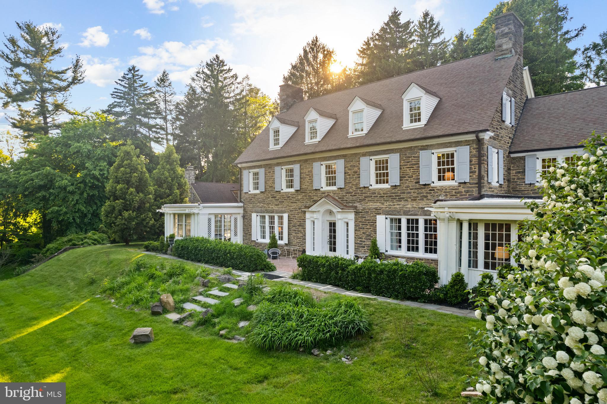This exceptional Wissahickon Schist estate was designed by Robert McGoodwin in 1919, and masterfully refurbished for today’s lifestyle. Set on nearly an acre just steps from the Wissahickon trails, the property offers 7,600+ sq ft of refined living, elaborate stone walls, blue stone and brick walkways, a potting shed, guesthouse, two-car detached garage, and an expansive parking court.

Inside, natural light fills every room. The main level includes a grand front-to-back entry hall, formal living room, dining room,  paneled library, all with fireplaces. A gourmet kitchen with butler’s pantry, and prep room, a sun-filled family room,  and a stunning pub room that opens to a south-facing brick terrace complete the main floor. The second-floor primary suite includes a sitting room, marble bath, and generous closets. Additional junior suite with private bath, two other bedrooms, updated hall bath, and a laundry room are all located on the second floor. The third floor has  three additional bedrooms, a family room / flex space, fully updated bathroom, and ample storage spaces.

Extensively updated, including kitchen, baths, windows, floors, landscaping, and a new four-zone heat pump system (plus a fifth in the guest house), with recirculated water radiator heat for year-round comfort.

A rare opportunity to own a landmark residence where historic architecture meets modern living—steps from the Wissahickon trails and just minutes to Center City, offering the best of both nature and city convenience.