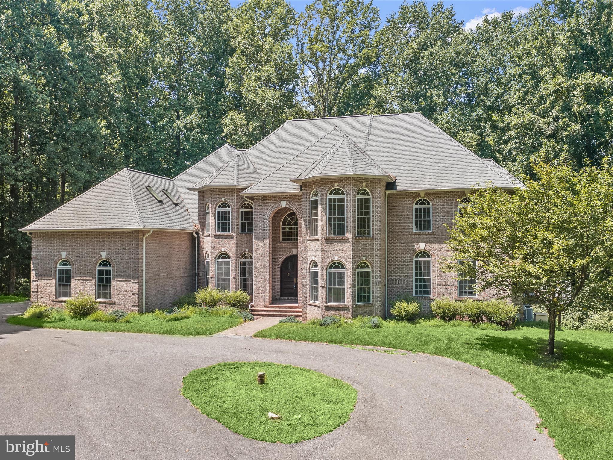 Welcome to this custom-built, contemporary brick castle, a secluded sanctuary at the end of a cul-de-sac, surrounded by lush, private woodlands. This stunning home is situated on a flat lot, perfect for entertaining, and features a Trex deck with a charming gazebo addition.  Upon entering, you're greeted by an imported solid Honduras mahogany front door, which opens into a grand foyer with Brazilian cherry hardwood floors that run throughout the home. The formal living room boasts soaring 20-foot vaulted ceilings, creating an awe-inspiring atmosphere.  The home features four contemporary arched propane fireplaces, adding warmth and elegance to the contemporary design. The gourmet kitchen is a chef's dream, with custom-designed cabinetry of varying heights, a double-towered pull-out pantry, and a seamlessly integrated refrigerator.  Both the lower and upper-level primary suites offer a luxurious retreat with whirlpool tubs in every bath, including spacious two-person jacuzzi tubs. The unique architectural design includes castle turrets in the front and a triple level of turrets in the back, ensuring no straight lines disrupt the fluidity of the home's layout.  The lower level is an entertainment haven, with two generously sized bedrooms and a movie room, perfect for family gatherings and relaxation.  This majestic home combines contemporary luxury with castle-inspired elegance, offering an unparalleled living experience in a private, tranquil setting.