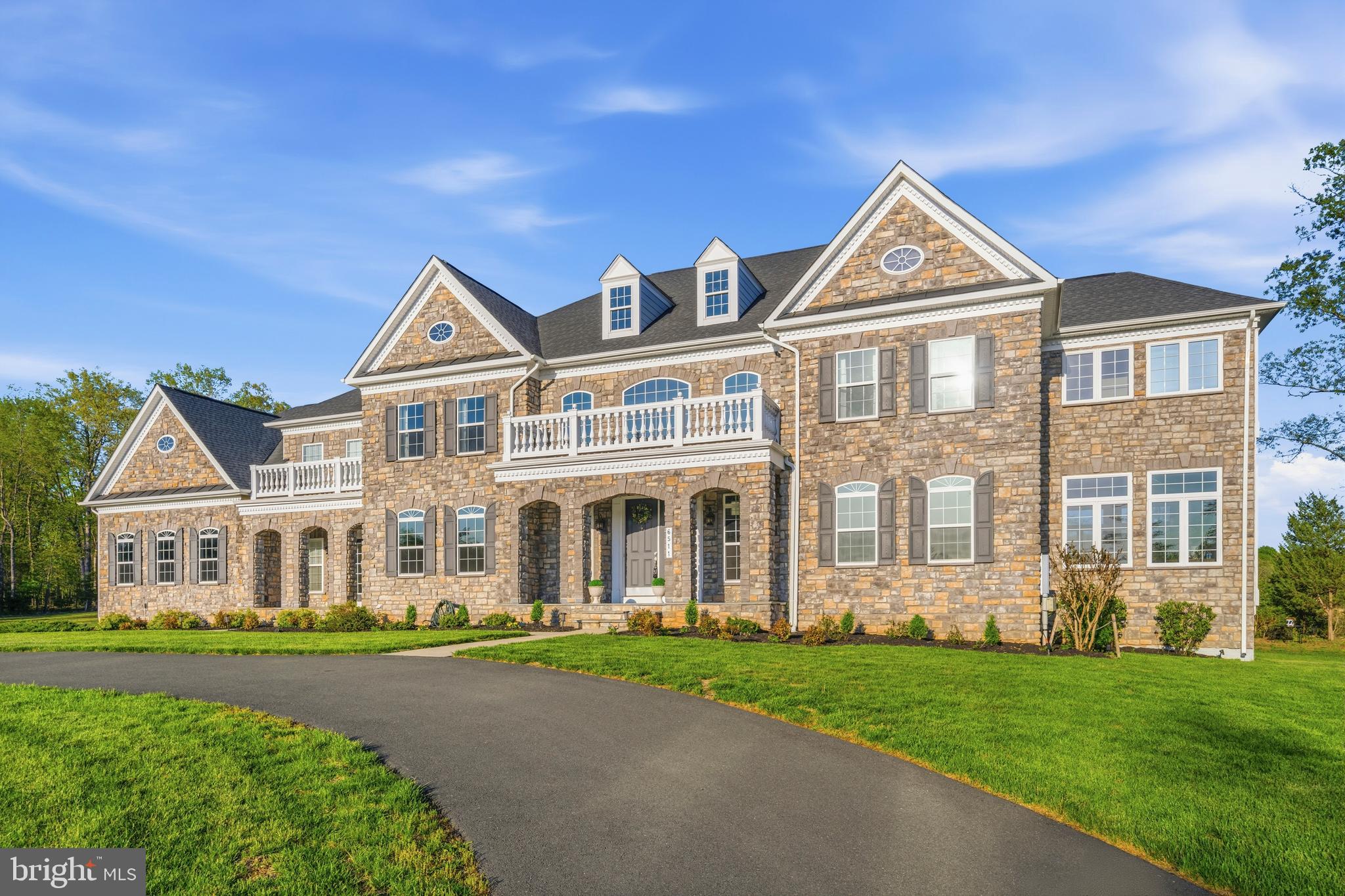 Set on an expansive 6.81-acre estate in the prestigious Hunters Pond community of Centreville, this exceptional Mt. Vernon model stands as one of the largest and most impressive homes in the neighborhood. Offering 6 bedrooms, 6.5 bathrooms, and three beautifully finished levels, this residence delivers a rare combination of luxury, privacy, and refined everyday living. 
From the moment you arrive, a grand circular driveway creates a striking first impression—both elegant and functional—guiding you seamlessly to the front entrance while providing ample parking and a dramatic sense of arrival that highlights the home’s stately presence.
Inside, a breathtaking two-story foyer welcomes you with dual curved staircases and rich Julian Hickory Sella hardwood flooring that flows throughout all three levels. The main level is thoughtfully designed to balance formal sophistication with everyday comfort, featuring a custom formal dining room, a refined formal living room, and an additional living space just off the sunroom—originally intended as a private office and now styled as a relaxed lounge.
A main-level bedroom (currently staged as a library) with a full bathroom offers flexibility for guests or multigenerational living. A well-designed mudroom with built-in storage and a second laundry room with hook-ups adds convenience to daily living.
At the heart of the home is a true chef’s kitchen. An oversized island with striking quartzite countertops anchors the space, complemented by premium appliances including a 48” Monogram professional range with 6 burners and grill, a 48” Monogram hood, built-in refrigerator, double ovens, microwave, warming drawer, and two dishwashers. The adjoining Butler’s pantry continues the same elevated design with matching quartzite countertops, custom cabinetry, backsplash, under-cabinet lighting, a prep sink, and a beverage refrigerator.
The family room is a stunning focal point, featuring a dramatic wall of windows, coffered ceilings, and a gas fireplace with a brick surround. A bay window seating area with built-in seating adds warmth and charm, while custom window film has been installed to soften natural light, reducing glare while maintaining a bright and comfortable interior environment.
Outdoor living is equally impressive. A custom stone patio provides the perfect setting for both entertaining and relaxation, complete with a built-in seating wall and a striking wood-burning fireplace that creates a cozy, inviting atmosphere year-round. The outdoor kitchen is equipped with a high-end built-in grill, generous prep space, and sleek stone countertops, all set against a private, tree-lined backdrop that enhances the home’s sense of tranquility and retreat.
Upstairs, the primary suite offers a true private sanctuary with hardwood floors, a tray ceiling, a floor-to-ceiling bay window, and a separate sitting area. Dual oversized walk-in closets provide abundant storage. The spa-inspired primary bathroom features a soaking tub, a separate stall shower, a private water closet, and an additional separate toilet—allowing for added comfort and functionality.
Each of the three additional upper-level bedrooms includes its own en-suite bathroom and walk-in closet. A dedicated upper-level laundry room adds everyday convenience.
The fully finished lower level is designed for both entertainment and versatility, offering a spacious media and recreation room, a wet bar with refrigerator and sink, a gym or workshop space, ample storage, and a sixth bedroom with a full bathroom—ideal for guests or extended living needs.
Additional features include a 4-car garage, 3-zone HVAC system, two water heaters, a water softener, and a well-maintained alternative septic system (serviced in December 2025).
This is a rare opportunity to own a truly distinguished estate where luxury, scale, and thoughtful design come together in one remarkable home.