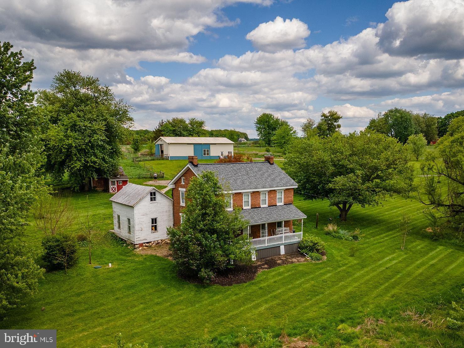 OPEN HOUSE THIS SATURDAY (6/6) FROM 1-3PM!! Your dream of a functional farmette on over 10 acres with classic brick farmhouse in Carroll County can be realized at 2100 Blacks Schoolhouse Road.. Warm, inviting, and with all main systems and roof completely recently updated, you'll enjoy all modern conveniences combined with the charm of yesteryear - but without the worry! The wonderful back porch takes you inside the main level, which features hardwood floors, newer appliances, an open country-style eat-in kitchen with wood stove, and plenty of room for a large table. A separate formal dining room provides flexibility for a first-floor office or playroom if preferred, while the adjacent living room is just off the kitchen. A half bath with washer/dryer and plumbing in place for a shower complete the first floor. With laundry also able to be relocated upstairs, the space provides plenty of opportunity for a second full bath or keep as-is! Upstairs,find three spacious bedrooms with wonderful natural light, a very large updated full bath with tub/shower combo, and walk-up access to the attic for additional storage. The house is painted in a neutral palette throughout and is just one of those cozy, inviting spaces you can't help but feel "at home" in. There is also a large summer kitchen attached under the porch that would serve wonderfully continued to be used as storage or renovated into additional living space - a primary suite, family room, office, or even attached garage! Outside, find multiple fenced pastures and a large, center-aisle barn with space for at least 4 stalls, equipment parking, water and electric, ready for your animals, homesteading accessories, parking - whatever you need! The topography is gently rolling with plenty of flat, usable acreage and the pasture is plentiful! Additional outbuildings include a shed and chicken coop, all in a pastoral setting with room to expand your vision - gardens, animals, equipment, future improvements, or simply open space to enjoy. Whether you dream of bringing horses home, starting a hobby farm, or settling into a slower lifestyle with room to roam, this 10-acre farmette is the perfect setting to plan your future chapters. Quiet, functional, and full of possibility - come explore the potential!