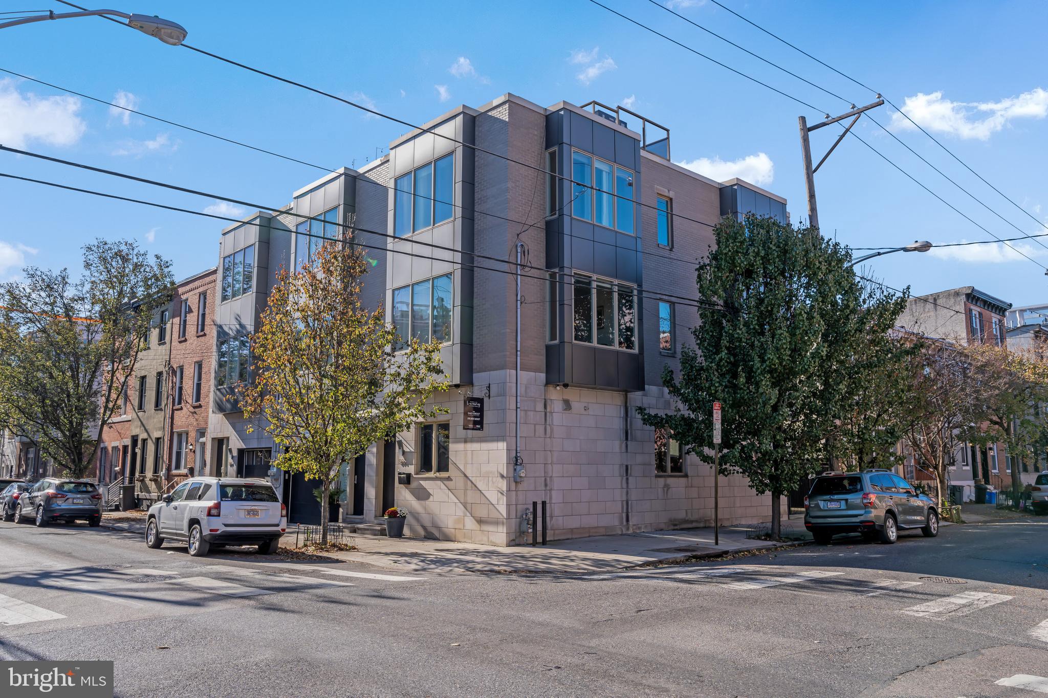 Positioned on a coveted corner lot in the heart of Graduate Hospital, this architecturally striking home offers the perfect blend of contemporary design, exceptional craftsmanship, and urban convenience. Built by one of Philadelphia's premier builders, this light-filled residence features 4 bedrooms, 2.5 baths, private parking, a finished media room, and an expansive rooftop terrace showcasing breathtaking 360-degree views of the Center City skyline.

Just outside your door, enjoy a highly walkable lifestyle with neighborhood favorites including Pub & Kitchen, Sidecar Bar & Grille, and Loco Pez, while the renowned dining, shopping, and green space of Rittenhouse Square are just a short stroll away.

The home's corner orientation and bay windows flood the open-concept living spaces with natural light. Soaring 11-foot ceilings, maple hardwood floors, and refined contemporary finishes create an elegant backdrop for both daily living and entertaining. The chef's kitchen is appointed with quartz countertops, a glass tile backsplash, and a premium suite of Wolf, Sub-Zero, and Asko appliances, anchored by a generous island with bar seating.

A dramatic wood-and-steel staircase leads to the upper levels. The luxurious primary suite offers a Juliet balcony, bay window, custom closet space, and a spa-inspired bath featuring marble tile, a quartz double vanity, and an oversized glass-enclosed shower. Two additional bedrooms, a flexible den or fourth bedroom, and beautifully appointed baths provide exceptional versatility.  Message to view today!