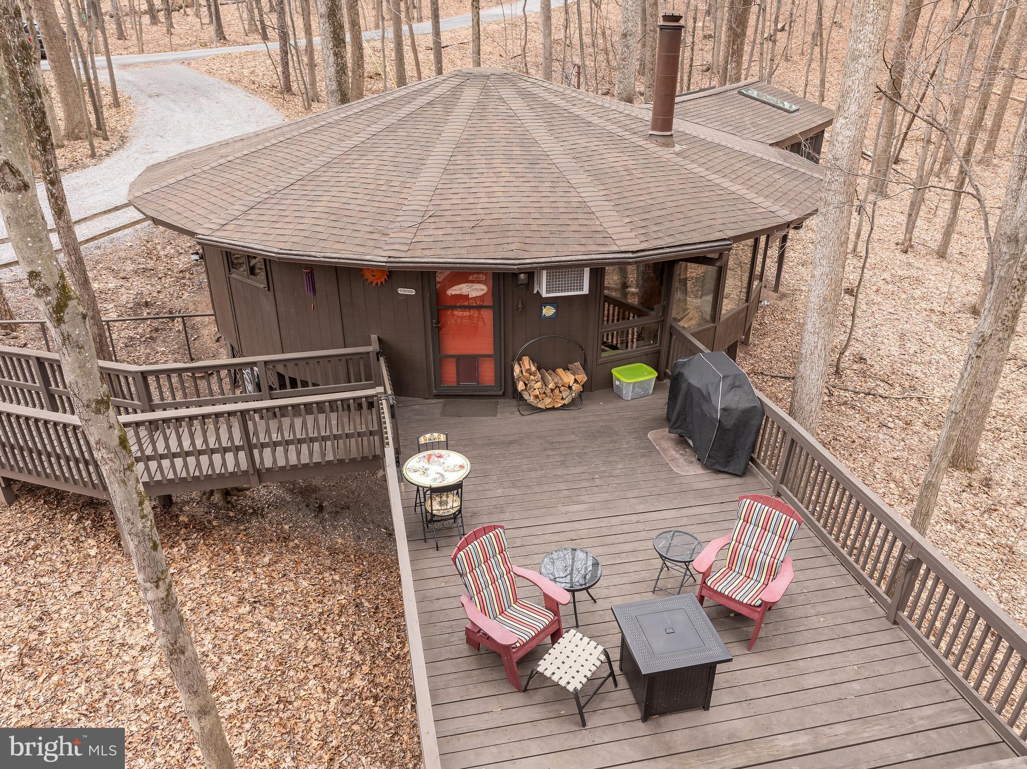 Who wants to live in a magical tree house? This enchanting hideaway will be coming soon to the market on Saturday, March 29! It boasts 2 large bedrooms, 1 1/2 baths. This stunning contemporary home is nestled on a wooded lot in The Woods Resort, offering the perfect combination of serene surroundings and a piece of nature's paradise. The round architecture design is unique in so many ways.  Just step inside and pleasantly discover a beautiful open living space, complete with  floor to ceiling windows and a center wood fireplace. These features bring the outdoors in -  creating an outdoor like setting, but also floods the space with natural sunlight...perfect for entertaining! The large covered porch is a great place to read, rest, relax, stargaze,  the possibilities are limitless.  As you enter the house, you'll find  a large open deck where you can enjoy the outdoors, take in the peaceful view or watch the deer as they pass by! This home has everything to offer including a Class B Membership to The Woods Resort;
With this membership, you have access to 2 outdoor pools, indoor pool, indoor and outdoor pickle ball, tennis ball, basketball, racquetball courts and a private fitness center. 
It's time to schedule your appointment today to view this amazing home!
