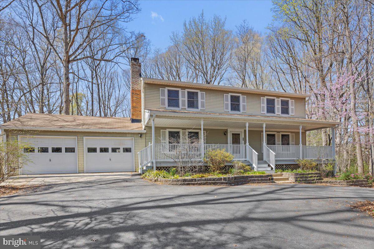 Welcome to this four bedroom two and half bath colonial home situated on 3.55 acres private acres. The lot is partially wooded with mature trees and still plenty of space for outdoor activities, gardening, and rear-deck lounging. This home offers the perfect combination of privacy and convenience. As you approach, you are greeted by a large front porch. As you enter, you immediately notice hardwood flooring throughout the entire main level and a traditional floor plan.  The main level offers the kitchen, family room with wood burning fireplace, formal dining room, formal living room, den addition, half bath, and laundry room with a convenient laundry chute. The upper level features a primary suite with en-suite bathroom with a walk-in shower and dual vanity. The entire upstairs has hardwood floors as well! Three additional bedrooms and a shared full bathroom upstairs complete this level. The full walk-up basement with wood stove can be used as additional living space and storage. Enjoy the added screened in porch and expansive deck, perfect for hosting summer get togethers. Convenient two-car garage with circular driveway offering plenty of parking. Ideal commuter location close proximity to Joint Base Andrews, Washington DC/Joint Base Anacostia-Bolling, Annapolis, and Alexandria, VA. Heat pump 2017,  Hot water heater 2016, Pressure tank 2023, Sump pump 2015, Radon 2015, Sunroom 2015, Deck 2010. Welcome home!