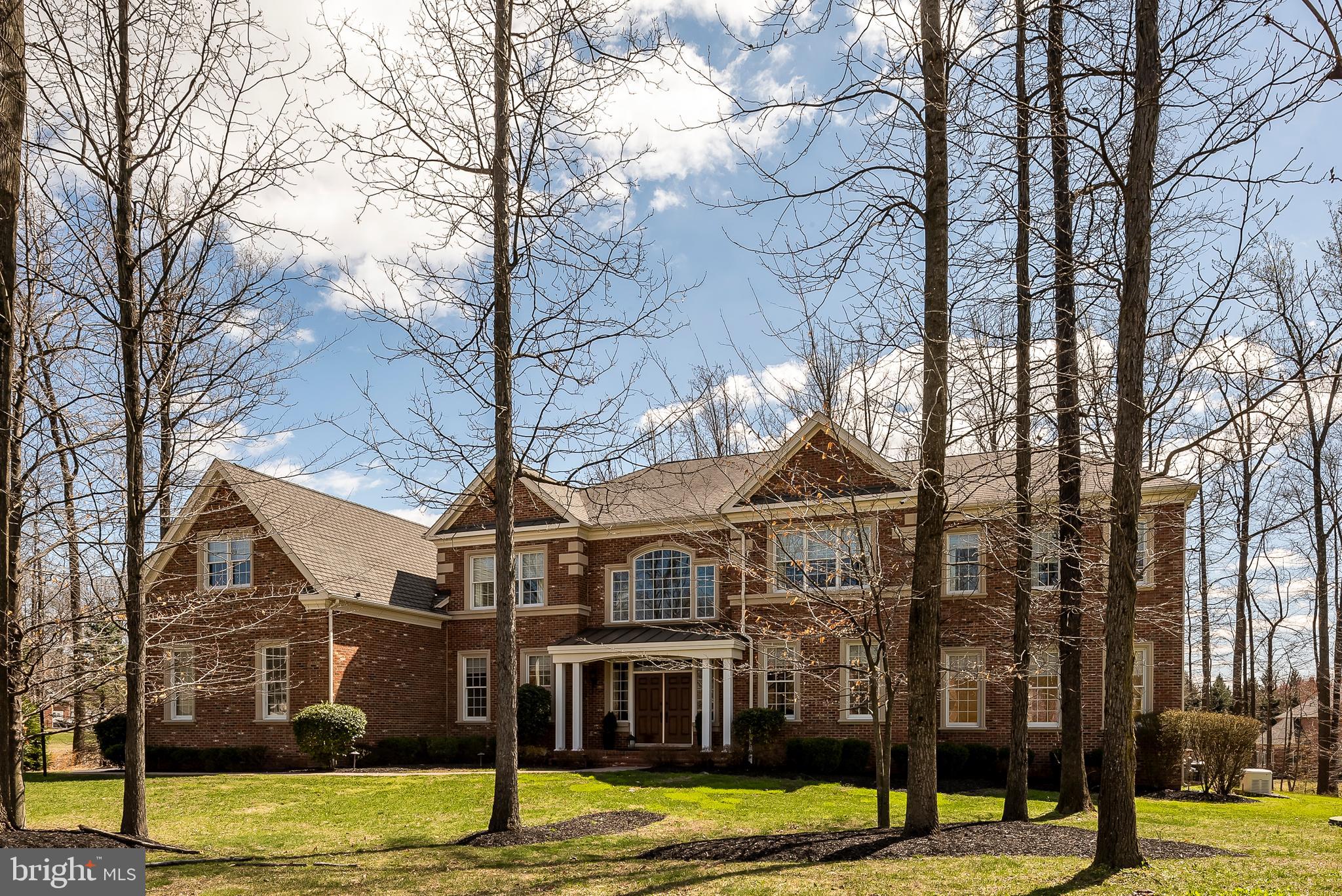 Beautifully crafted all brick Henley Model by Toll Brothers Homes offers over 11,000 square feet of living space and boasts a two-story foyer and double turned staircases that frame the view into a spacious Great Room with a gas stone fireplace. The entranceway features light porcelain tiles with a black galaxy border and giving the feel and warmth of an informal country manor. The Great Room has a coffered ceiling stained to bring out the natural wood grain, matching a built-in entertainment center and plantation shutters. Brazilian cherry wood floors are throughout the first and second floors. Cooks and party hosts will love the heart of this home with its exceptionally large well-appointed gourmet kitchen. There is generous counter space, a granite island with a prep sink, a granite breakfast bar, a walk-in pantry, and an expansive octagon morning room with a cathedral ceiling. This dream kitchen has top of the line stainless steel appliances, including a professional-grade GE Monogram gas stove, refrigerator, built-in microwave, and wall oven. The breakfast area has a built-in granite desk and opens to a huge 700 square foot deck complimented by an outdoor sound system. A powder room is located off the kitchen. Ten-foot ceilings create an open and spacious feel. A rear staircase from the Great Room leads to the upper level. From the foyer, one can see the living and banquet-sized dining rooms and French Doors leading to a sunny conservatory surrounded by windows. A striking focal point of this home is found at the top of turned staircases. An unparalleled library wrapped in mahogany stained book shelving and tray ceiling and corner window seating is enhanced by a handsome chandelier. This custom library combines formality and comfort and easily hosts anything from a board meeting to a good game of chess, or simply a lovely getaway for a relaxing read! The Grand primary bedroom suite includes a private den with a columned entry, a three-sided gas fireplace, tray ceiling, and windows providing a bright and airy feel. The primary bath features a huge soaking tub with a tray ceiling above and is flanked by his and her granite vanities. Opposite the tub is a large stand-up shower with dual shower heads and two private water closet areas. There are two custom walk-in closets with closet systems PLUS a stunning walk-in closet that spans over the three-car garage featuring Brazilian cherry wood flooring and yet another gorgeous custom closet system. There is a full-size laundry room off the primary suite with custom shelving. Among the three other bedrooms on the upper level, two of the bedrooms are as large as most primary bedrooms, easily accommodating king-size beds each with an ensuite bathroom. The large third bedroom shares a full bath with the impressive custom office suite bordered by two closet systems with shelving and drawers and built-in file storage on either side of the office. This area could be easily converted to another bedroom or playroom if desired. The lower level is an entertainer's dream! There is a main recreational area with a stone gas fireplace, double-wide walk-up, and a spectacular granite wet bar with a full-sized refrigerator, cooktop, and cabinetry.  A full bath and a second laundry room are next to the bar area. Opposite the bar is an unbelievable exercise room complete with special flooring and set up for televisions on the walls! On the other side of the stairs is a multipurpose area featuring a den, guest room, and full bath. Perfect for an office, playroom, or possible nanny suite. A Bose sound and stereo system are found on all levels. The backyard has plenty of room to add a pool and there are a large front and side yard as well! An underground irrigation system and exterior lighting is another enhancement. A lot of thought and detail were put into this home with many hidden extras like the bibbs insulation in interior walls and between floors for energy efficiency and soundproofing!