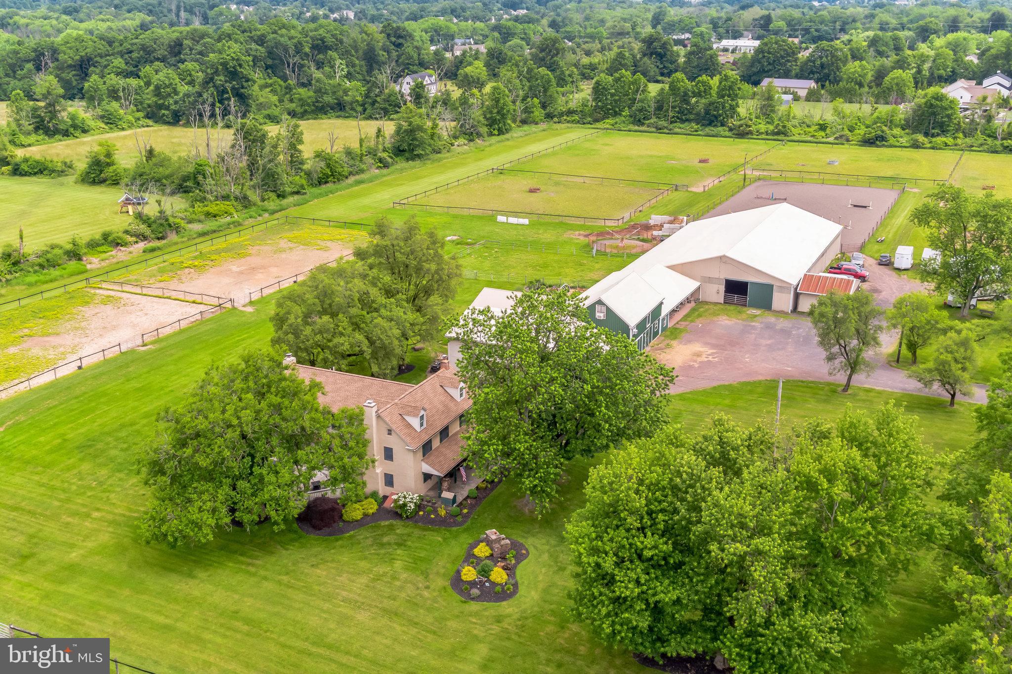 This enchanting farmhouse boasting an exceptional front porch is poised on nearly 13 acres in Hilltown Township and attractively blends the charm of the original 1780 house with a functional floorplan necessary for today’s lifestyle.  During the planning of the addition and renovation of the existing home, every effort was made to preserve the old-world charm of the original house. Wide-plank yellow pine flooring, deep window sills and all the nooks and crannies expected in a residence of that era can still be found. The living room, with its beautiful stone fireplace and wood insert, and the dining room, ,with its built-in mirrored serving cabinet and two large closets, both have distinctive farmhouse ceiling beams.  A remarkable floor-to-ceiling stone wall is the dramatic focal point of the kitchen.  The kitchen also features solid cherry cabinets, granite countertops, stainless appliances, and a cheery breakfast area bright with many windows where the new homeowner will certainly enjoy a morning cup of coffee. The family room offers a traditional raised-hearth wood-burning stone fireplace and access to the deck.  Watch your horses graze while barbecuing on the expansive secluded 530 sqft  two-tiered side deck bordered by mature landscaping.  A mudroom with washer, dryer and laundry tub is found on the barn side of the home, making it convenient to take off your barn boots and overalls before entering the main house. Ascending the turned staircase to the 2nd floor, double doors at the top of the steps open  to a primary bedroom suite which has a spacious walk-in closet, a sizable bathroom with two sinks, Jacuzzi tub and separate shower. Three other bedrooms and full bath complete the 2nd floor.  If anyone should require extra space for a playroom or storage,  the walk-up attic is found in the back hallway of the original house and is just begging for your finishing touches. There isn’t an inch of carpeting in the home, which benefits those with allergies or pets.  Very important updates and features not to be overlooked include a new roof on the house May 2024, new HVAC system 2022/2023, newer oil tank and heater flue, and an electronic dog fence allowing your pups six acres of freedom. This farm is an equestrian delight, as there is a 60’X120’ indoor arena, two tack rooms, 25 stalls, 7 which are heated, a kitchenette, nine pastures with solar-powered electric fencing, a round pen and hot walker.  Tack up and enjoy the trail that surrounds the pastures!  Aside from the couple of stalls occupied by the Sellers’ horses, the remaining stalls are leased.  For those interested in this country setting but are not equine enthusiasts, the indoor arena doors open wide for those needing to store large equipment, hobby cars or a treasured boat. An additional shed can be found adjacent to the indoor, so equipment storage is not an issue.   The heated/cooled 1.5 car garage   is currently utilized as a workshop and features 220 three-phase electric, high ceilings and bright 8’ LED lighting; it is without question an ideal spot for working on your motorcycle or race car. Two one-bedroom apartments, one with an enclosed porch and the other with a bonus room, are located above the barn. There is ample parking in the front and around the side of the barn.   This farm is located within 30 minutes of the Bucks County Horse Park, so trailering to the Thursday Morning Horse Shows or Tuesday Evening Dressage is convenient. It’s also just minutes to enjoy the loop around Lake Galena, or all the quaint shopping and terrific eateries found in Doylestown, Lahaska and New Hope. Pride of ownership is evident, as the current property owners have thoughtfully updated and lovingly cared for the house, barn, pastures and many horses over their 29 years.  Be it your forever home or your weekend equine dream-come-true, this type of property is rarely offered and one not to miss. Act 319 preferential assessment. 24 hour notice required.