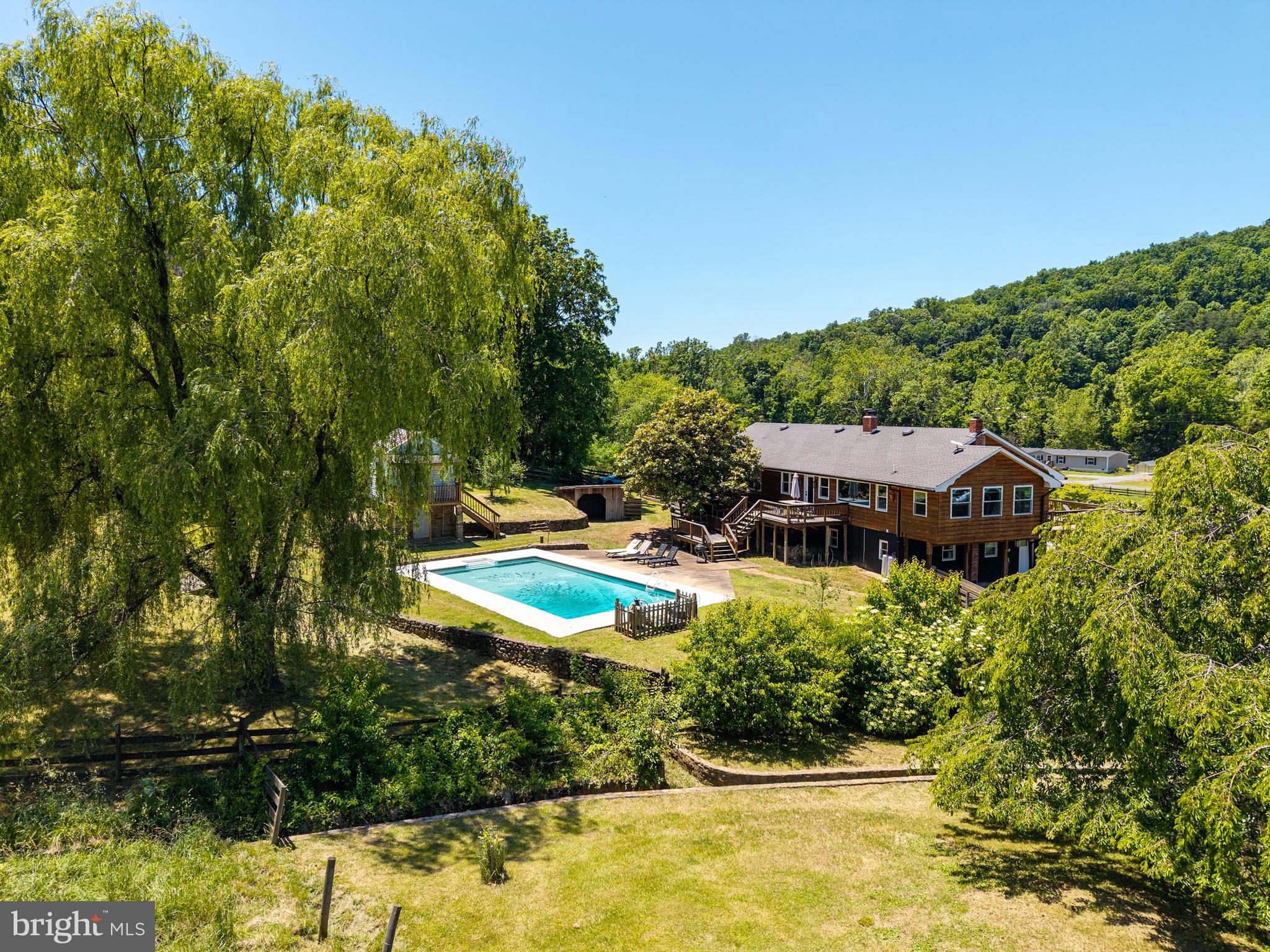 This expansive 68 acre estate is divided into 4 land parcels and offers a multitude of investment opportunities, or a wonderful retreat to call your own!  A main house with over 4000 square feet of living space, a bank barn, a 1400+ square foot guest house, glamping tent area, in-ground pool and scenic walking paths and nature trails. The main house seamlessly blends luxury with rustic charm. The heart of the main home features an open floor plan with a gourmet kitchen, boasting upgraded countertops, a six-burner gas stove, and a spacious island, perfect for culinary enthusiasts. Indulge in the serene views of mountains, pastures, and tranquil ponds from the inviting deck or porch. The property is equipped with a personal in-ground pool, ideal for relaxation and entertaining. Equestrian enthusiasts will appreciate the multiple board fenced pastures, automatic waterers, and large bank barn. The guest house layout includes a main suite with large bathroom, two additional bedrooms, and a second full bath. Separate laundry/mudroom and an open great room for the kitchen, dining, and living room.  The guest house construction is completed through drywall, and most of the finishing fixtures are already purchased and included.  A short walk from the hub of the property will take you to a meadow with a platform canvas “glamping” tent area. Enjoy a fun evening of camping under the stars by the fire pit and roasting marshmallows in your own slice of nature.  The back part of the property is still undeveloped and has trails for hiking or ATVing, two ponds, and multiple open meadows. The main house has a 5 bedroom installed septic, guest house has a 3 bedroom installed septic, and the 23 acre parcel has a 3 bedroom septic certification letter.  No HOA, town taxes, or deed restrictions.  The main house is ready to be used as a short term rental if desired!