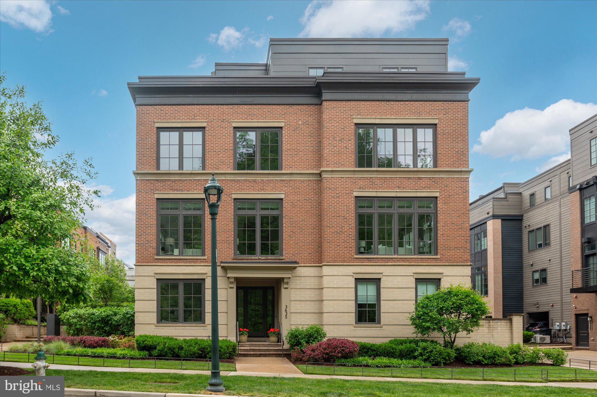 Sought-After End-Unit EYA Brownstone in the Heart of Chevy Chase Lake
Tucked into a quiet, wooded enclave and overlooking parkland and a stream, this beautifully appointed home offers a rare combination of peaceful surroundings and walkable convenience to the vibrant shops and restaurants at Chevy Chase Lake.  This premier end-unit residence features over 3,000 square feet of living space, 4 bedrooms, 3 full baths, and 2 half baths, along with floor-to-ceiling windows on three sides that create bright, open living spaces filled with exceptional natural light throughout the day. Tall ceilings throughout the home further enhance the airy and elegant feel of the interior.  A large two-car garage with solid-wood custom built-ins added by the current owners, and a private elevator serving all levels, provide exceptional ease of living. The entry level includes a spacious office, powder room, and coat closet.
The main level offers expansive open-concept living, including a gracious living room with a gas fireplace, an additional powder room, a generous dining area, and a gourmet kitchen with a large island, along with a casual family room area just off the kitchen—perfect as an extension of the space for everyday living and entertaining. Motorized blinds on the main level add privacy, convenience, and sophistication.
The bedroom level includes a sun-filled primary suite with two walk-in closets and a spa-like bath with dual vanities and radiant heated floors. Motorized blinds in the primary bedroom add an additional touch of comfort and luxury. A second bedroom features an en-suite full bath, while the third bedroom is currently used as a den. A conveniently located laundry room with a front-loading washer and dryer completes this level.  The top floor adds exceptional flexibility with a fourth bedroom, full bath, and a comfortable secondary living space that opens directly to the large rooftop terrace featuring a wet bar, built-in gas grill, and fireplace—creating the perfect setting for entertaining or relaxing at the end of the day.  End-unit homes in this community—offering this level of light, privacy, and setting—are highly sought-after and rarely available. Please come experience all that this special home and community have to offer.