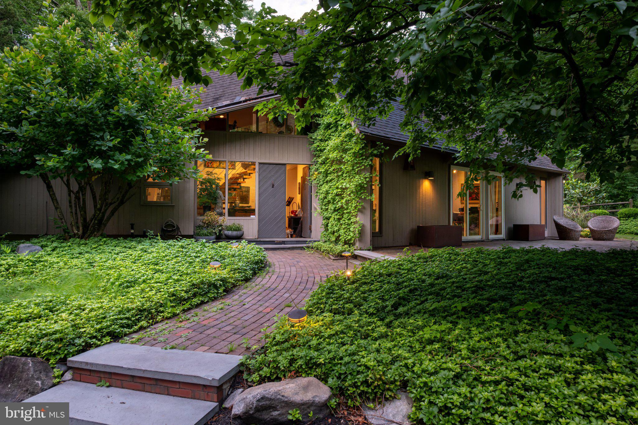 A long, winding driveway carries you through lush forest, the woods closing in tighter the further you go. Then you cross a quaint stone bridge over Dark Hollow Run, the trees fall away, and the landscape opens onto a secluded mid-century modern retreat. Built in 1984, the 1.5-story, 2,210-square-foot contemporary home includes an in-ground pool, a two-car attached garage, and an additional detached two-car garage with storage. It sits on approximately 11.93 acres, only minutes from local amenities and the charming riverfront boroughs of New Hope and Lambertville.

Upon entry, a slate-stone foyer showcases a floating staircase. To your left is a great room with vaulted ceilings, hardwood floors, and a custom triangular skylight that fills the room with natural light. Make your way back toward the foyer and through to the family room, where sliding glass doors overlook a sweeping, manicured lawn. A wood-burning fireplace sits center stage beneath the canopied second floor. From there, a showstopping, multi-purpose sunroom and dining room await, wrapped in skylights and windows along their full length, where you can take in the vast beauty of nature and wildlife on these grounds. A sliding glass door gives you access to the backyard stone patio and pool. The kitchen is the heart of the home, thoughtfully laid out for everyday cooking and entertaining alike. A wall of oversized windows floods the kitchen with light and views of the backyard and pool. The dark cherry custom cabinetry, paired with natural stone countertops and stainless appliances, makes for a sophisticated palette. The bar is tucked off to the side, with a full wine rack above, a sink, and a beverage refrigerator. To finish the first floor, the half-bath is down the hall along with the laundry center stacked in the closet and access to the two-car attached garage. Lastly, the primary bedroom suite has vaulted ceilings, a custom walk-in closet, and a primary bathroom featuring a dedicated shower, a soaking tub, a makeup area, and his-and-hers sinks. The second floor is a sanctuary in and of itself, with a layout that includes a sitting area with access to the outdoor roof deck, overlooking the pool area and offering another sweeping view of the landscape. A well-appointed office complements the space, along with a second bedroom offering a reach-in closet and its own access to the roof deck. The third room could serve as guest quarters or storage, with a reach-in closet.

The real value is the land. Nearly twelve acres, gently sloping and wooded, with the detached garage offering real potential for a future guest house or studio beyond the storage it provides today. The grounds are the kind of blank canvas that lets a buyer decide whether to restore this 1980s original to its full character, or bring forward an entirely new design and make it your own.

Located in the award-winning New Hope-Solebury school district, this is a rare offering of usable, private acreage minutes from one of Bucks County's most sought-after river towns. Land, privacy, and architectural bones like this do not come around often in Solebury Township. This is the kind of property that makes you remember why Solebury is considered one of Pennsylvania's most desirable destinations.