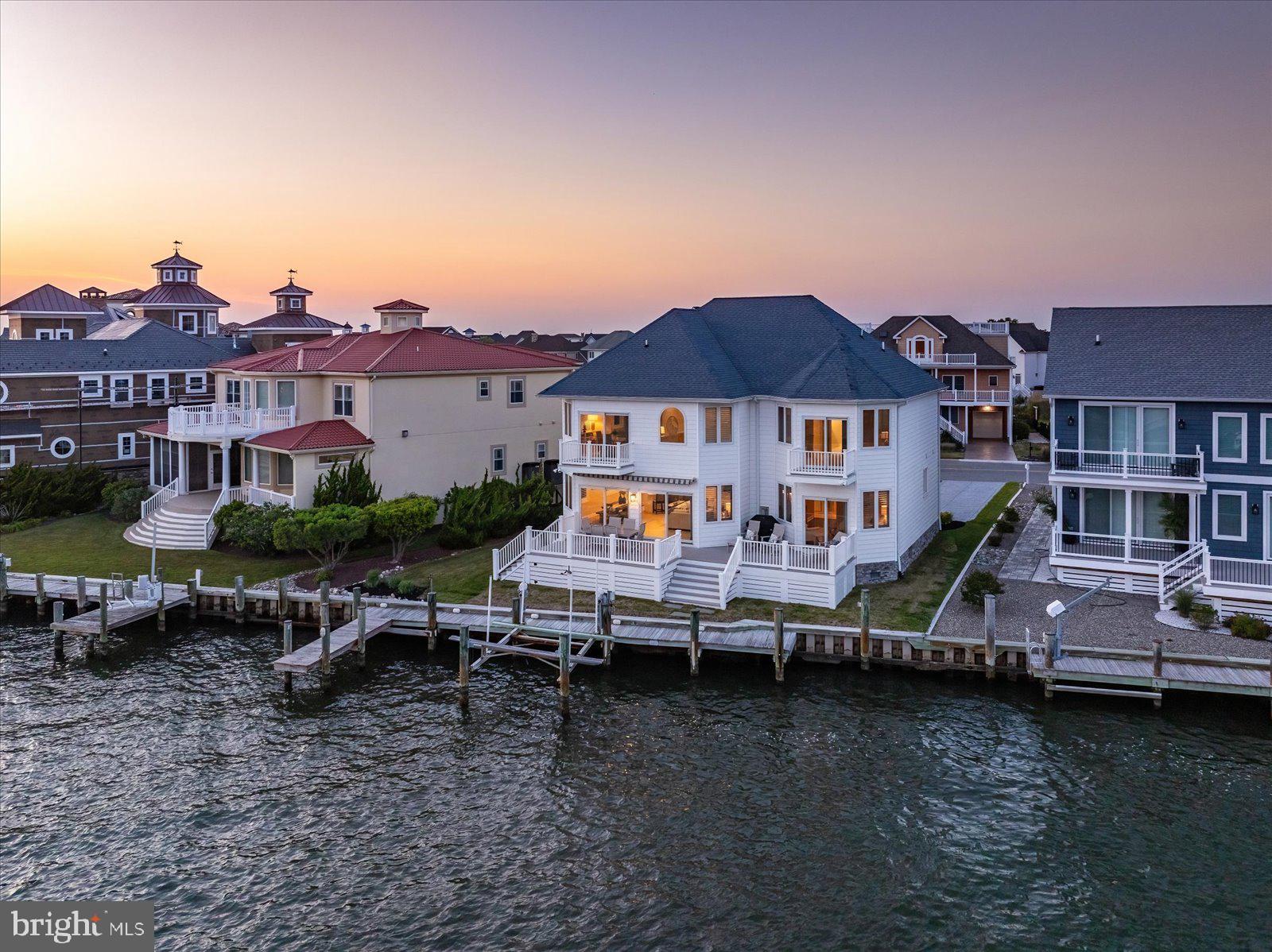 Experience direct waterfront living with breathtaking bay views in this stunning luxury 5-bedroom, 3.5-bath single-family home in the sought-after Heron Harbour Isle community. A charming white exterior sets the tone with a classic coastal, nautical vibe, complemented by beautiful new navy-blue front doors. Perfectly positioned on the water, the home includes a private boat slip with lift and a vinyl bulkhead—ideal for boating enthusiasts. Enjoy magnificent sunsets from the spacious family room, featuring a cozy gas fireplace for year-round comfort, a wet bar for entertaining, and a wall of windows and glass sliders that flood the space with natural light while showcasing panoramic bay views. Step outside to the expansive waterfront composite deck with southern exposure, complete with an electric awning—perfect for relaxing, grilling, or hosting unforgettable crab feasts as boats drift by. The chef’s kitchen impresses with elegant quartz countertops, abundant cabinetry, and crisp white finishes.  The dining area overlooks the water as well. The first-floor waterfront primary suite offers a private retreat with stunning views, direct deck access, walk-in closets, and a luxurious en-suite bath featuring a soaking Jacuzzi tub and a separate tiled shower. The main level also includes a half bath and a convenient laundry room. A second living area or office opens to a private balcony overlooking the water on the second floor. Upstairs, one bedroom boasts its own waterfront balcony, while additional bedrooms are thoughtfully designed with Jack-and-Jill baths for convenience. There is also a bonus room that could be used as a 6th bedroom or home office or playroom. This home is packed with upgrades, including 40-year architectural shingles, heated tile floors, 2x6 exterior wall construction, upgraded lighting and landscaping,  and a two-car garage.  Dual-zone heating ensures year-round comfort, with gas heat on the first floor and a heat pump on the second. Residents of Heron Harbour Isle enjoy resort-style amenities, including indoor and outdoor pools, a kiddie pool, fitness center, sauna, tennis courts, and scenic sidewalks and piers. Embrace the ultimate coastal lifestyle with boating, fishing, crabbing, kayaking, and paddleboarding right from your backyard.