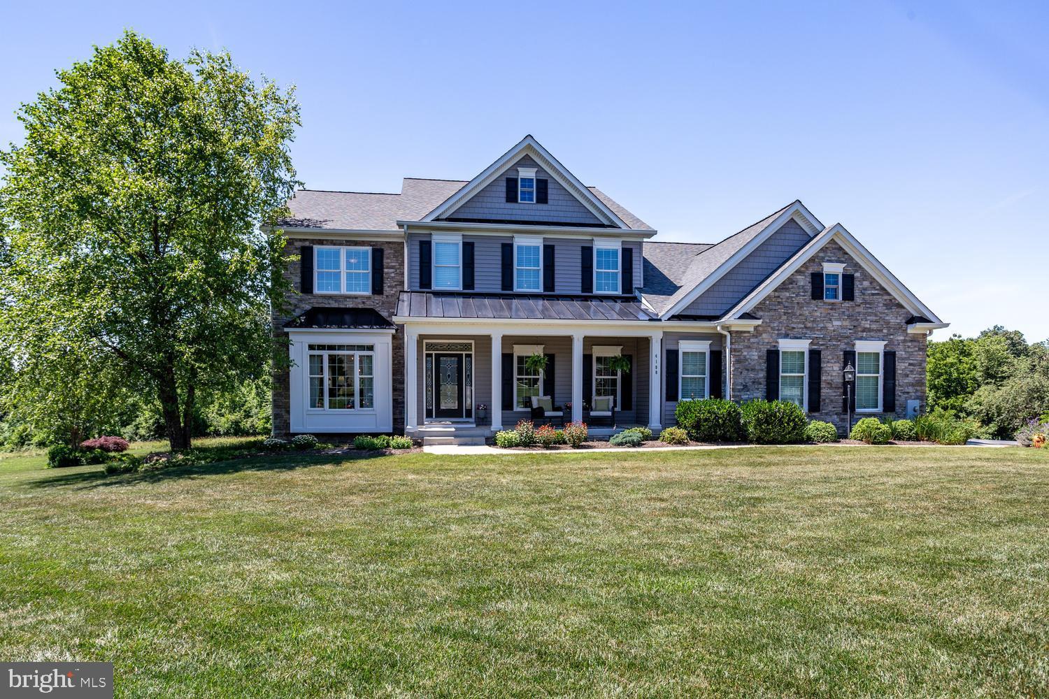 Welcome to 4180 John Benjamin Drive, a custom-built natural light-filled estate with dual geothermal HVAC systems, an elevator for all 3 levels and fabulous In-Law/ADU space nestled on 7.09 picturesque acres in Caroline’s Crossing. With entertaining and family fun in mind, this exceptional property features lots of open yard, multiple acres of woods and a lovely (33’ x 16’ ) heated in-ground pool surrounded by a concrete pool deck and natural stone coping. Pool is approximately 3' to 6' deep, includes a safety barrier cover, new pump (2024/2025) and robotic cleaner. A charming front porch and pretty stone and vinyl exterior create exceptional curb appeal, complemented by 8' tall garage doors and beautifully landscaped grounds. Leaded glass front door framed by 2 sidelights and a transom window lead to the entrance Foyer featuring shadow box molding and a classic hardwood cascading staircase. 9' ceilings (excl. BR and BA's over garage) and hardwood flooring throughout the Main Level enhance the home’s spacious feel, while wide windowsills and beautiful millwork details add timeless elegance. High quality Milgard windows throughout. Off the Foyer, a charming Library offers built-in shelving and cabinets as well as an expansive Living Room and Dining Room. At the heart of the home is a gourmet chef-inspired Kitchen with expansive granite countertops, tumbled-stone tile backsplash, 2 islands (including a dine-at island with seating for 8), 3 sinks, abundant 42-inch cabinetry with custom storage features, stainless steel appliances, propane cooktop framed by a custom wood range hood, wall oven, warming drawer, built-in microwave, dishwasher, French door refrigerator and a walk-in Pantry closet.  Just beyond the Kitchen, enjoy the Breakfast/Sun Room with 6 windows and transoms and a slider leading to the composite deck with a SunSetter awning (2023/2024). Adjoining Butler’s Pantry with cabinets,  mini fridge, prep sink and room for a coffee station. The Family Room offers a stunning coffered ceiling, recessed lighting, a propane gas fireplace, and access to the composite screened porch (25'3" x 13'7") with new screening (2026) and cathedral ceiling. Upstairs, hardwood flooring extends through the landing and hallway featuring a large linen closet (7'x3'). The Primary Suite features a tray ceiling, Sitting Room (or a great nursery), walk-in closet (13'6"x11'5") and spa bath with BainUltra hydro thermo massage air jet tub, double bowl vanity, and custom tile shower with multiple shower heads.  Bedrooms 2 and 3 each include a private bath and large walk-in closets. Potential Bedroom 4 is currently configured as a home office with awesome built-in work-from-home space, a sink, mini refrigerator and cabinetry. Convenient 2nd floor Laundry Rm includes LG front-load washer and dryer, utility sink, and cabinetry. The fully finished walkout Lower Level is ideal for multi-generational living, featuring full size above grade windows and a walkout slider with integral blinds, 2nd full Kitchen with quartz countertops and stainless appliances, spacious Great Room, a private Primary Suite with an ensuite full bath including a separate shower with ceramic tile surround and soaking tub, 2 additional bedrooms, new carpet (2026), a full bath, and a separate Laundry Room with a laundry sink . Utility Room (17'x13') offers a pair Water Furnace Envision GeoThermal heating/cooling system (2012), Bradford White water heater (2022). Additional highlights include 36" wide interior doors, lever door handles, a 3-car garage, Tesla EV charger, dual 200-amp electrical panels equipped with generator plugs and mechanical interlock kits to support backup power options, 325 gal propane tank and abundant storage. Exterior accents-NEW roof, roof gables, tin roofing and shake siding (2021). Opportunities like this are rare - 7+ acres, luxury amenities, elevator access, and a resort-style backyard create a truly unforgettable place to call home!