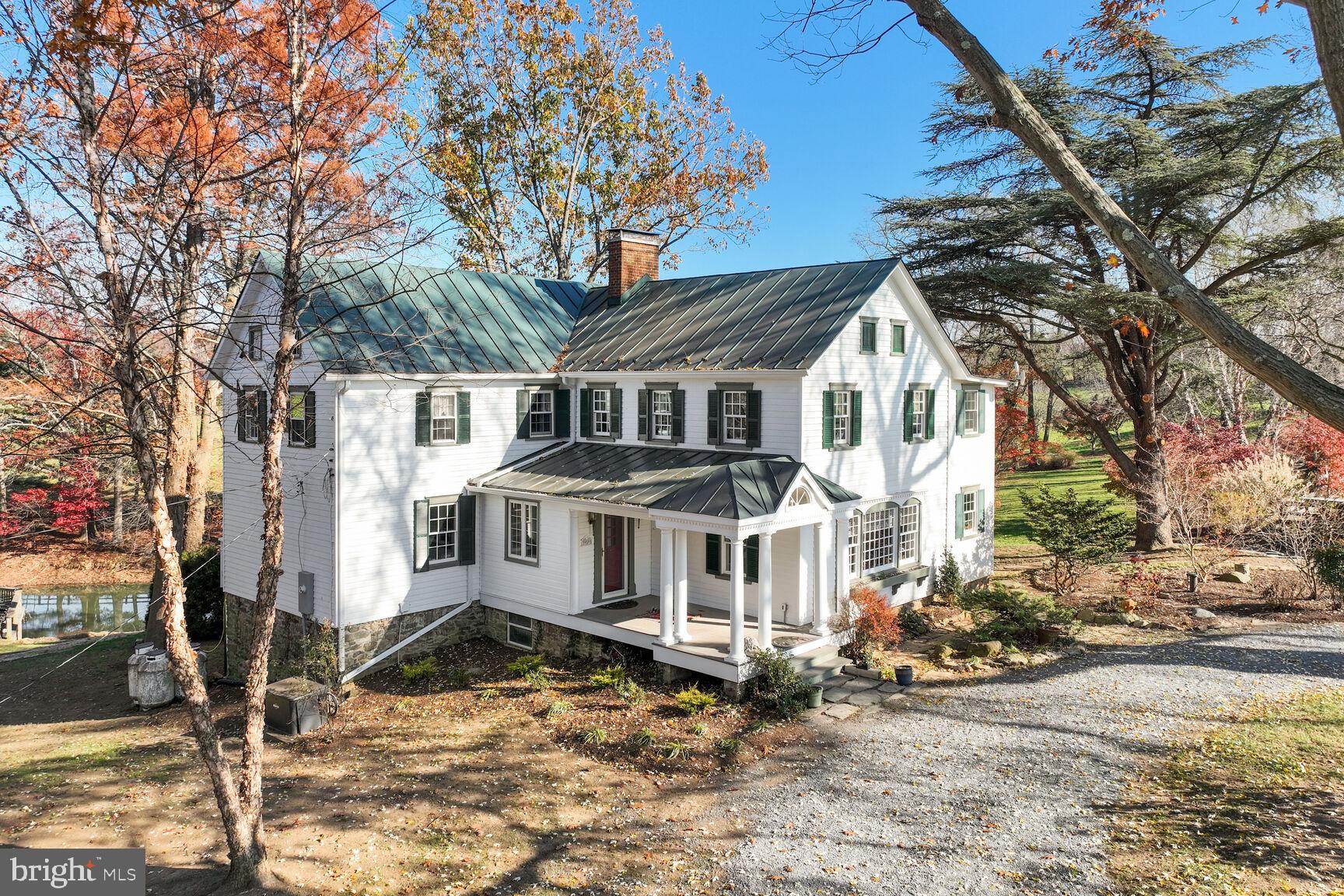 Nestled between the short hills of the Blue Ridge Mountains and the Potomac River, there lies a
hidden gem that boasts a world of possibilities. Traipse around the 28-acre property and you
will discover rolling pastures, a planted fruit orchard, a half-acre spring-fed pond, and a vineyard
that looks out over unblemished vistas in all directions. Protected by a Conservation Easement
through the Land Trust of Virginia, Weatherlea Farm gives you the feeling of stepping back in
time, only two miles from the center of Lovettsville VA’s growing shopping district. Half a mile
further down the road, a quick trip across the Potomac puts you in Brunswick Md, where the
MARC train can bring you to Washington, DC in an hour, or a 20- minute drive will take you to
Frederick, MD
The farmhouse acts as the centerpiece of the property with 4-bedrooms, 5-bathrooms built in 1790. There are two additional dwellings, the Shepherd’s Cottage & the Milk Cottage, both perfect for long or short-term tenancy. The property has 2 pasture run-in sheds, a 3-stall barn, and another barn designed to store farm equipment and a workroom, with space for an artist’s loft above. A main attraction, however, is a pre-Civil War era bank barn with a stone foundation. Down below, there is space for 4-6 stalls; above is an authentic but upgraded area that has functioned as a wedding and event venue for 15 years.
In the 1800s, the approximately 250-square-foot structure doubled in size, when the footprint
was expanded. The upper floor was expanded upward, turning it into a two-story structure. The main floor is now a beautiful library with a Western facing picture window, a fireplace, and custom-built floor to ceiling bookshelves. On the upper floor, much of the interior  log construction remains exposed, capturing the historic interest of the home and creating a gorgeous and unique primary suite.
In 1950, the property, which had become a busy dairy operation called “River’s Edge Farm,”was bought by Earle and Yetive Weatherly. They lovingly exposed and restored interior log walls and added more windows. Finally, they added a new front porch to make a grander
entrance to the home which they renamed “Weatherlea.”

The current owners purchased the property in 1992. In the early 2000s, they upgraded the tiling
and granite in the kitchen, added yet another upstairs bathroom, and replaced the small
sunroom with a larger one that sits atop a basement level atelier. From there, one can walk out
into the terraced gardens behind the house. In the 2010s, a new metal roof was put on the
home, and a geothermal HVAC system was submerged in the pond. The most recent renovation came in 2019, when the front portion of the two-story porch was enclosed to create a master bath above a ground floor laundry room and a mudroom off the kitchen. This enabled more sections of the original exterior log cabin walls and windows to be exposed and restored, once again enhancing the historic beauty of the home. During this process, the stone foundation was dug up and re-sealed and waterproofed. These most recent upgrades added closet space, created a sleeping loft in one of the bedrooms and enabled the house to accommodate a family of five. It also gave each bedroom a full bathroom, with an eye toward possibly converting the house into a bed and breakfast in the future.

To maintain its rustic beauty, the Conservation Easement was established in 2008. The property
shines throughout the year with flower beds, raised vegetable gardens, walkways, rock walls,
gazebos and a deck overlooking the pond. Over the years the pastures have nurtured horses,
sheep, llamas, and cows. The fields have been put to agricultural use for hay, and in 2001, an
acre-and-a-half of wine grapes were planted. Harvests of Weatherlea grapes have been sold to
local wineries and have made their way into several award-winning vintages.

Sellers Not Responsible for any potential rollback taxes