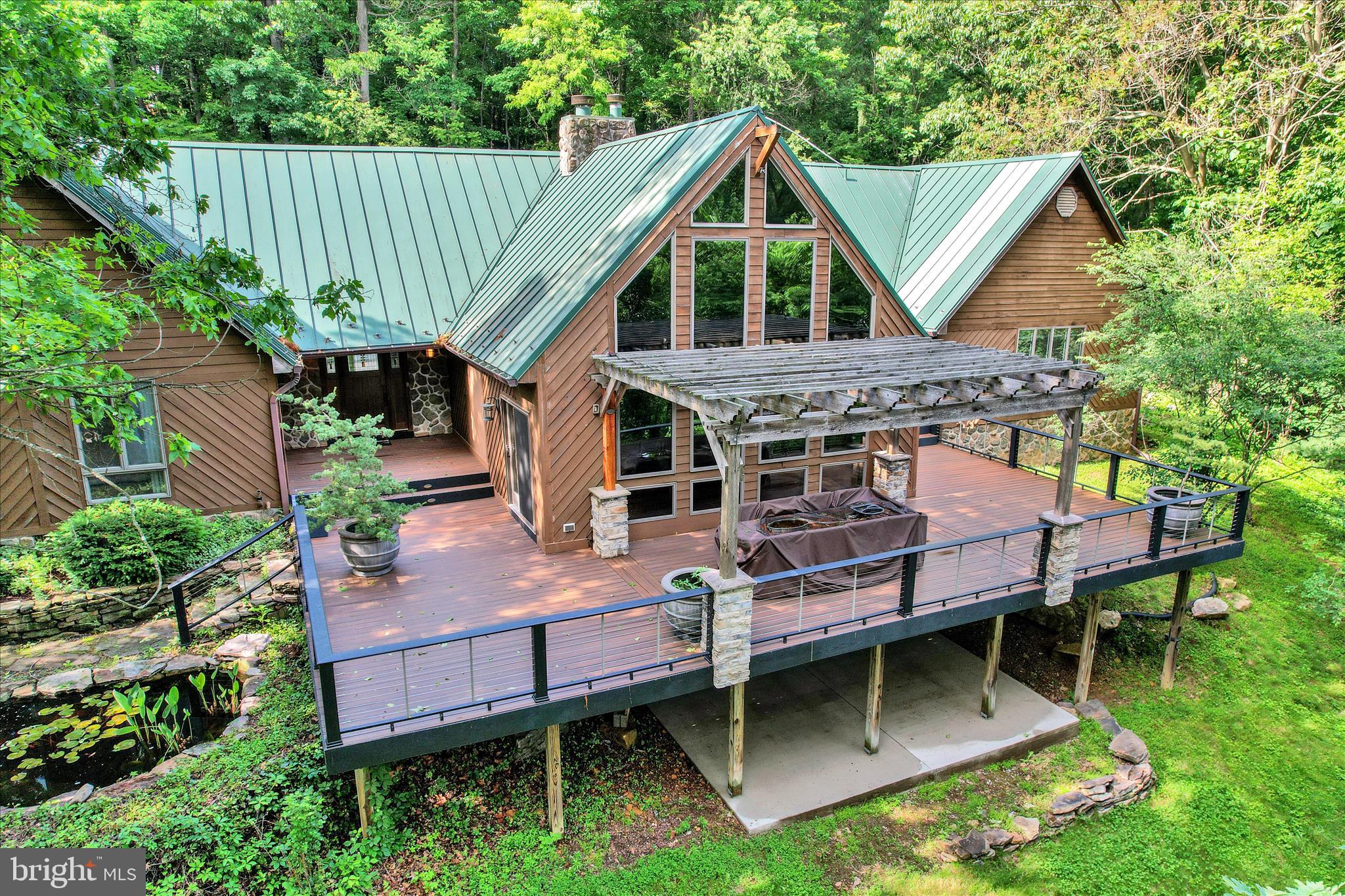 Nestled on 12.81 private wooded acres in York, PA, Dallastown Schools... this extraordinary custom ranch-style Craftsman estate offers over 5,500 square feet of luxury living designed with exceptional craftsmanship and timeless architectural beauty. From the moment you enter, soaring vaulted ceilings, exposed beams, dramatic floor-to-ceiling windows, and a stunning stone fireplace create a breathtaking first impression while filling the home with natural light and serene woodland views. Property is in clean and green. At the heart of the home is a true gourmet chef’s kitchen thoughtfully designed for both everyday living and entertaining. Featuring custom quarter-sawn white oak cabinetry, rich soapstone and granite countertops, two oversized islands, and premium upscale appliances, this remarkable space combines warmth, elegance, and functionality in every detail. The open-concept layout flows seamlessly into expansive living and dining spaces, creating the perfect setting for gatherings large and small. Step outside to the oversized deck overlooking the peaceful natural surroundings — an ideal retreat for morning coffee, outdoor dining, or quiet evenings immersed in nature.  The luxurious primary suite offers a private spa-like sanctuary complete with vaulted ceilings, tranquil views, and a stunning European-inspired wet room featuring an oversized walk-in shower, soaking tub, and refined designer finishes. An incredible boutique-style walk-in closet provides exceptional storage and organization.  With 5 bedrooms, 3.5 bathrooms, and a versatile bonus room/den perfect for a home office, gym, or media space, this home offers flexibility for modern living. Three of the bedrooms feature private en-suite bathrooms, offering comfort and privacy for family members and guests alike. The partially finished basement adds additional entertaining and recreational space while maintaining ample storage opportunities.  Blending refined luxury with rustic sophistication, this one-of-a-kind property delivers resort-style living, unmatched privacy, and extraordinary craftsmanship — all just minutes from the conveniences of York.