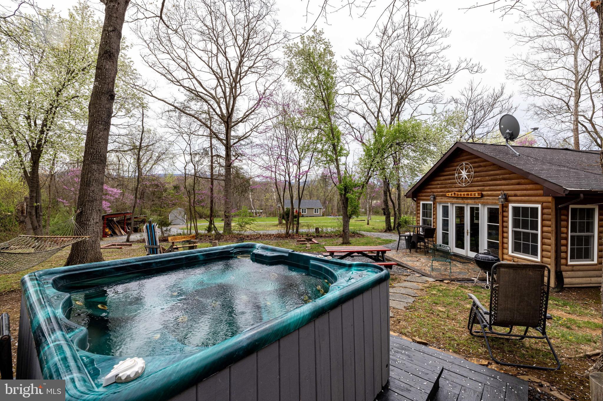 Welcome to Whitefish Cabin adjoining the George Washington National Forest and with its close proximity to the Shenandoah River and charming Town of Luray. Whitefish Cabin is a classic stone cabin which offers the perfect blend of rustic character and modern comfort. Situated on two separate lots combined for over 1.5 acres, with private community access to the Shenandoah River only 500 feet away, this 2-bedroom, 2-bathroom cabin is ideal for a full-time residence, second home, or a turn-key investment property. In fact Whitefish Cabin is already operating as a successful vacation rental (STR), with the potential to build an additional rental unit on the extra lot included in the sale — or to simply enjoy the added privacy / acreage.  Inside the cabin you will find two inviting living areas, LVP flooring, butcher block countertops, a cozy wood-burning fireplace, and a bright sunroom that allows you to truly enjoy the beauty of all four seasons. Additional perks include a washer and dryer, and that most inside and outside furnishings convey!  Valuable outbuildings, lean-tos, and a nearly new shed provide multiple storage options! Outside you can unwind in the hot tub, gather around the firepit, or spend your evenings relaxing on the covered porch in nature in the adjoining George Washington National Forest. Utilities are community water, a shared septic system with the adjoining cabin, with a recorded easement in place, and soil work has been completed by a licensed soil scientist on the extra lot included in the sale enabling another rental unit to be constructed in the future if desired. There is no active HOA! This is a rare opportunity to own a peaceful cabin retreat, with strong rental income potential, in one of the Shenandoah Valley’s most desirable locations. Adventure awaits you at Whitefish Cabin!