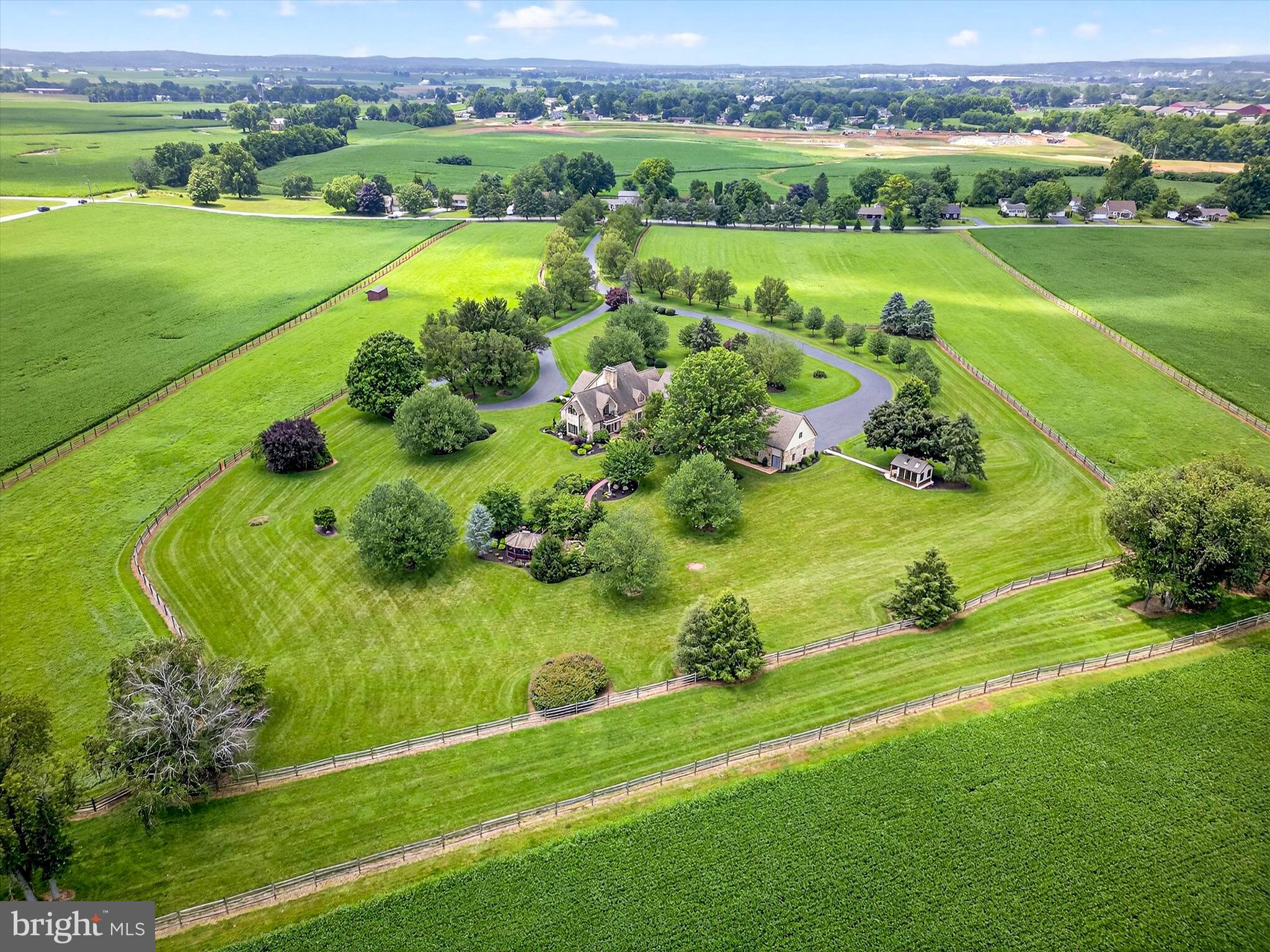 Welcome to this meticulous equestrian estate, set on 23 stunning acres in scenic Annville, Pennsylvania. Designed with equestrian amenities and serene country living in mind, this gated and fully fenced property combines privacy, comfort, and convenience. Enjoy a tranquil setting surrounded by natural beauty, all while remaining close to the vibrant attractions of Hershey, nearby arts and recreation, and some of the country’s finest dining. For effortless travel, the location has easy access to major highways, the Pennsylvania Turnpike, Harrisburg International Airport, and Amtrak. A long, tree lined driveway winds through beautifully landscaped grounds, leading to an elegant main residence and thoughtfully planned equestrian facilities. Inside, the home has six bedrooms, seven full bathrooms, and two powder rooms. The main level welcomes you with hardwood floors in the living room, complete with a gas fireplace for cozy, relaxing evenings. The formal dining room is an ideal space for hosting special occasions, with additional gathering areas throughout the main level providing flexibility and charm. The family room features stone tile flooring, built-in shelving, and a second gas fireplace, creating a warm and relaxed atmosphere for everyday living. The gourmet kitchen is designed to impress with granite countertops, a center island, top-of-the-line stainless steel appliances, and a bright breakfast nook. Whether preparing a quiet meal or entertaining a crowd, this kitchen is suited for both. A main level bedroom with a private bath is perfect for guests or family, while a second staircase leads to both the upper and lower levels. Upstairs, the expansive primary suite is a true retreat. Vaulted ceilings, a private balcony, and a generous walk-in closet create an elegant and peaceful space. The suite boasts two stylish bathrooms, one with a shower and the other with a shower and soaking tub, making it a quiet spot to relax and unwind at the end of the day. Four other bedrooms and three full bathrooms on the upper level provide ample accommodation, including one bedroom with a versatile bonus room currently used as a music space. The fully finished lower level continues to impress, offering a spacious recreation area, a custom bar with seating and a beverage cooler, and an exercise room with a full bathroom. A private sauna with seating delivers the ultimate in wellness and comfort right at home. A newly epoxied floor on the three-car garage adds a nice touch too! Outdoor living is equally inviting as indoor, with a stone patio accessed directly from the kitchen and family room. Enjoy every season with a covered dining area and firepit, while a nearby path leads to a charming footbridge over a tranquil pond and a peaceful screened gazebo for quiet moments surrounded by nature. For equestrian enthusiasts, the property is truly a dream come true. A separate gated entrance leads to a private, well equipped equestrian center, complete with a nine-stall barn with a washroom, an outdoor riding arena, fenced paddocks, two run-in sheds equipped with automatic waterers, and a second barn with additional storage and a private flex space with a half bath. A tenant house adds more living space and functional flexibility, with two bedrooms, one full bathroom, and a laundry area. This extraordinary estate is a rare combination of timeless beauty, exceptional amenities, and equestrian functionality. With expansive indoor and outdoor spaces, panoramic views, and a setting designed for year-long enjoyment, it’s a place where both people and horses can thrive in comfort and style. Schedule your private tour today to experience this unique property.