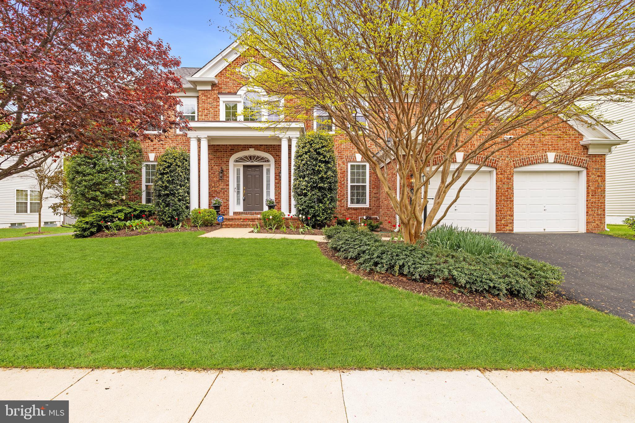 Welcome to 8167 American Holly Road, a stately Remington model in Lorton’s highly desirable Laurel Hill. This is a grand 5-bedroom, 4 and a half bath colonial built by Pulte Homes. It’s got great curb appeal with its impressive 4-columned portico overlooking the classy brick stoop. Add to that the just-sealed driveway, the appealing landscaping aided by a 6-zone sprinkler system and a roof that was new in 2021 with Leaf Relief gutters and downspouts installed in 2022. The roof comes with a fully transferable 50- year warranty. Elegant Oak Gunstock plank flooring greets you in the dramatic two-story foyer with its soaring Palladium window and flows through the main and upper levels. High ceilings add a feeling of volume. Extensive moldings detail the living room and dining room which also has columns framing its entrance. There are front and back staircases leading upstairs. The main-level office has glass-panelled French doors, chair, crown and box moldings, two windows and recessed lighting, making it the perfect spot to work from home. In the exceptional eat-in kitchen you’ll see rich cabinetry, an island with an overhang for bar stools, Corian counters and premium stainless appliances. The GE Profile double-oven, GE Profile 5-burner gas cooktop and LG refrigerator were new in 2023. The large kitchen window was replaced in 2023. Step through the sliding glass door (replaced in 2022) to the lovely TrexAccents deck, a perfect spot for grilling, entertainment or just relaxing. No neighbors behind, just pretty trees! In the family room off the kitchen, four windows flank the gas fireplace with its brick surround and detailed wood mantel. Heating and A/C is a 2-zone system with one zone new in 2019 and the other in 2017. Upstairs you’ll find 5 spacious bedrooms and 3 full baths plus a much-loved laundry chute! The lavish owner’s suite has a tray ceiling with crown molding and 4 tall windows. In the owner’s bath, there’s a dual-sink vanity, a deep-soaking tub, separate shower, large walk-in closet and linen closet. The huge lower level has a full bath, lots of storage, a big bonus room, an oversized rec room with recessed lighting and steps up to the rear yard. This fine home is close to all major transportation routes, shopping and restaurants.  Laurel Hill residents have access to a wide range of community amenities including an outdoor swimming pool, tennis courts, walking paths and an elegant clubhouse.