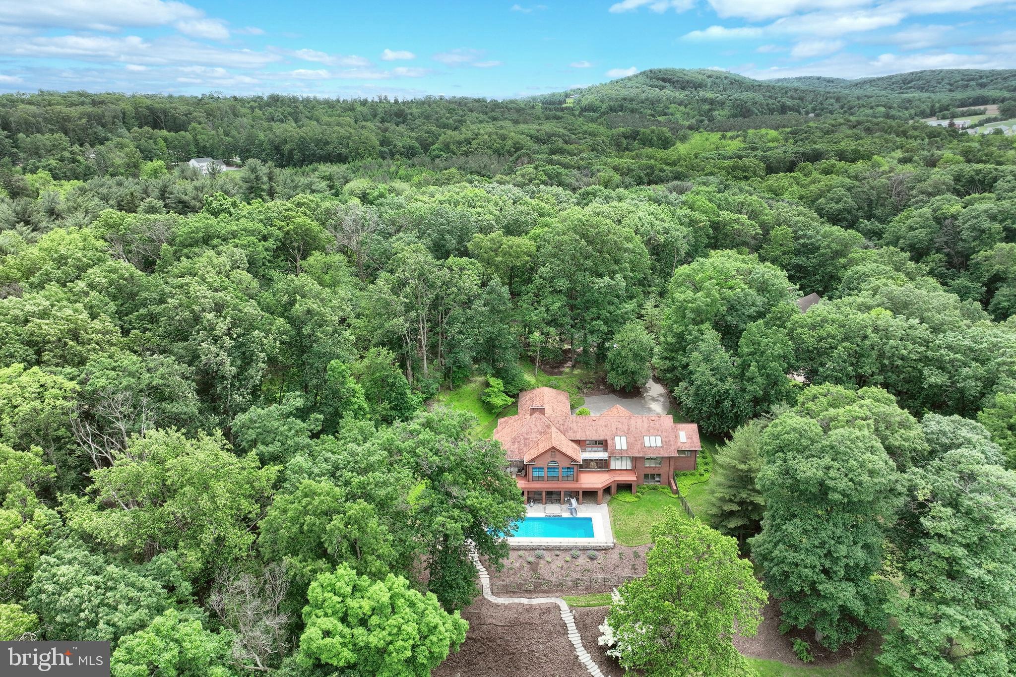 Welcome to a rare one-of-a-kind lakefront estate in the prestigious Lake Pahagaco.  Privately set on over 7 breathtaking acres with approximately  405 feet of direct lake frontage, making it a nature lover's dream and an entertainer's paradise.  This exceptional property offers the perfect blend of luxury, privacy, and resort-style living where every day feels like a getaway.  As you approach this custom-built rancher, you'll be captivated by its elegant architecture, showcasing quality craftsmanship from top to bottom. The residence features a striking open floor plan, expansive windows, soaring ceilings and skylights fill the home throughout while showcasing spectacular lake views from many rooms. Every detail has been thoughtfully considered, from the solid walnut doors and trim to the mood lighting that complements the home's inviting atmosphere. Spacious gourmet kitchen, perfect for culinary enthusiasts, featuring high-end appliances, granite counter tops and generous prep space and walk-in pantry.  Retreat to the luxurious  primary suite, with a spacious dressing room with generous closet space. The en-suite bathroom features a spa like bath, walk-in shower, double sinks and large soaking tub ensuring a private
Each of the additional 5 bedrooms are generously sized, offering plenty of room for family and guests. Cozy up in the large great room in front of the beautiful stone woodburning fireplace and dining area.   Adjacent to the great room, a unique room with curved greenhouse windows offers endless possibilities—ideal for an artist's studio, gallery, office. The fully finished lower-level features 3 full baths and 4 large bedrooms to fit a crowd.  Family room featuring a gas fireplace, wet bar and expansive game area all walking out to the pool area.  Imagine hosting gatherings by the saltwater pool, equipped with top-of-the-line features including a slide and hot tub, all while enjoying the picturesque backdrop of your private lakeside paradise.
Venture outdoors to the expansive redwood deck that surrounds the lakeside of this all-brick home with hardy redwood trim, cedar shake roof, with copper gutters and spouts. The beautifully landscaped grounds, enhanced by landscape lighting and a dedicated sprinkler system, guide you to the tranquil lakefront, where you can enjoy fishing, boating, or simply soaking in the serene views. Plus, homeowners have exclusive access to the association beach, picnic area, and a boat barn with electric—perfect for enjoying all that lakeside living has to offer.  Situated on a peaceful cul-de-sac, with seamless connection to nature combined with luxurious amenities, this incredible property is a rare find.