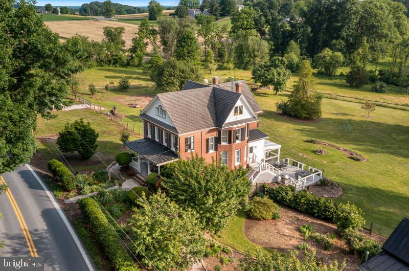 SUBDIVIDABLE PLUS 2 HOUSES!  Welcome to Walnut Spring Farm in the Heart of the Hereford Zone — a truly special 11.7-acre property offering endless possibilities. This property conveys a  2–3 acre subdivision right or the option to place the land into preservation, this estate also includes a second dwelling — a charming carriage house that features a one bedroom loft, full bath, living room, laundry room, eat in kitchen, wood stove, privacy fenced patio area — adding even more versatility and value.  The property is ideal as a homestead, multi-generational retreat, or legacy estate. Step inside the gorgeous four-level brick Victorian Farmhouse and be greeted by a spacious open foyer with hardwood floors and a beautiful turned staircase. The main level features high ceilings, a dining room with pocket doors, a living room with wood stove, built ins & pocket doors, a family room, and a large kitchen that flows into a sunny breakfast room overlooking panoramic countryside views. Second staircase in the kitchen leading to the  second level, boasts three large bedrooms, a separate office/bonus, and a newly renovated full bath featuring a clawfoot tub, walk-in shower. The third upper level offers a cozy private primary suite with a living area and wood-burning stove, office space, bedroom, full bath with walk-in shower, laundry room closet. The full basement includes a half bath, 2nd laundry hook-up, and generous space for a workshop, gym, or additional storage — ready to be customized to your needs. Outside, you’ll find a screened in deck area to relax and enjoy the views. A large bank barn with six stalls, multiple paddocks with run-in sheds, and several outbuildings. A spring-fed stream runs through the property, providing year-round water access for animals. Previously used as a horse and alpaca farm, the land offers both functionality and beauty. Pool/hot tub and all dwellings/outbuildings being sold AS-IS.