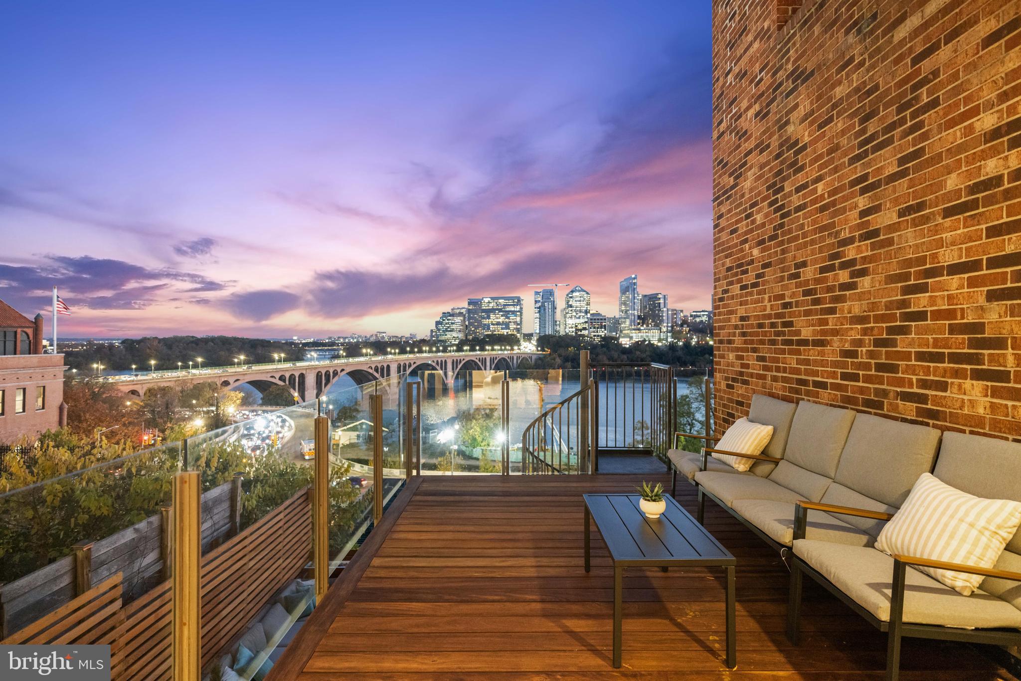 Perched high above the Potomac with sweeping, panoramic river & city views, this exceptional Georgetown residence stands peerless in the marketplace and truly defines elevated living. Refined architectural details adorn the property throughout, with south-facing floor-to-ceiling windows and doors on every level that open to multiple decks with both dining and lounge sections and uninterrupted, breathtaking vistas of the river and skyline on every level - including the Key Bridge, the Rosslyn skyline, the Lincoln Memorial, the Kennedy Center, and the Washington Monument.

Encompassing more than 3,500 square feet over four dramatic levels, this extraordinary home designed by esteemed architect Henry Goodfellow Hunt features three bedrooms, three full bathrooms, and two half bathrooms, effortlessly balancing grand scale with intimate comfort. The expansive main living room level is an entertainer’s dream, distinguished by soaring 10’ ceilings that accentuate its openness and grandeur. A gas-burning fireplace with a mantle clad in the same Indiana limestone used on the National Cathedral serves as a striking centerpiece, complementing the breezy indoor-outdoor flow that invites guests to gather and admire the stunning views.

An elevator services all floors, culminating in the upper-level primary suite where Washington’s most captivating panoramas unfold in spectacular fashion. The primary features a gas fireplace, a large walk-in closet, and a renovated bathroom replete with luxurious finishes. From the top-floor vantage point, the river and cityscape unfold in cinematic fashion, creating an atmosphere of unparalleled tranquility.

Two spacious bedrooms and two full bathrooms occupy the third floor, offering privacy and flexibility for family and guests. Each bedroom is enhanced by beautiful natural light and is thoughtfully designed for comfort and ease of living. Additional highlights include a renovated chef’s kitchen, a one-car garage, and more than 800 square feet of outdoor living space ideal for al fresco dining, tranquil morning coffee, or entertaining guests while overlooking the Potomac River.

Perfectly situated at the end of Georgetown’s West Village and just minutes from the airport, this residence is walkable to neighborhood favorites including 1789 Restaurant, Fitzgerald’s cocktail bar, the iconic Cafe Milano and the boutiques and cafés that define Georgetown charm. Rare and remarkable, this home represents a once-in-a-generation opportunity to own one of Washington’s most magnificent views.