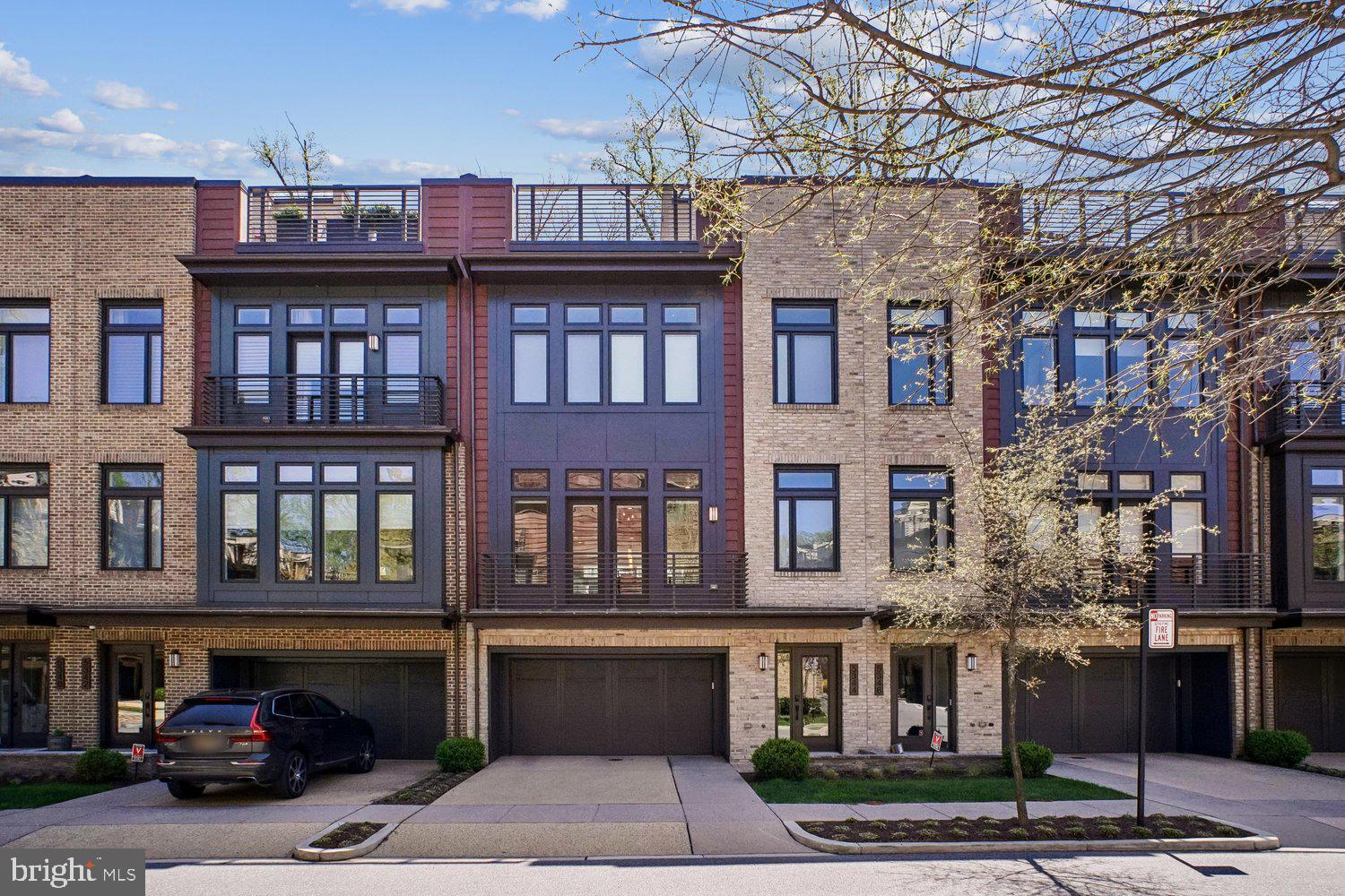 Experience refined townhome living in coveted Grosvenor Heights. This exceptional EYA Harrison model offers three features distinguishing it from other models in the neighborhood: a full driveway providing 2 parking spaces in addition to the EV equipped 2-car garage, a fully fenced rear yard for privacy, and beautiful treed views from every level and the rooftop deck. Offering approximately 3,400 sq. ft. of finished space, with an elevator-served layout designed for comfort and convenience. The sunlit main level showcases dramatic 10-foot floor-to-ceiling windows and is ideal for entertaining, with a gourmet kitchen, oversized island, spacious dining area, and a great room with a fireplace. The entry level includes versatile living options with a full bath—perfect flex space for a home office, guest suite, additional family room, art studio...the possibilities are endless. Upstairs, 9-foot ceilings accentuate the airy feel, with a privately situated primary suite on one side and two additional bedrooms with a full bath on the other—an ideal layout for everyday living or guests. Thoughtful finishes throughout reflect EYA’s award-winning craftsmanship. Enjoy low HOA fees and exceptional convenience—less than a mile to Grosvenor Metro, the Bethesda Trolley Trail, Fleming Park, Wildwood Shopping Center, Grosvenor Market, Strathmore Hall, and major routes including I-495 and I-270. Sophisticated but comfortable, sunlit, and superbly located—this is a rare offering in Grosvenor Heights.
