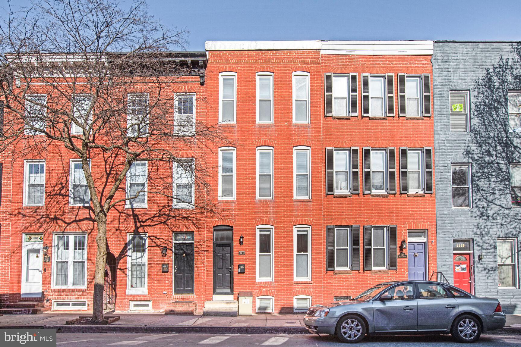 This extra-wide row home blends historic character, modern comfort, and unique features that set it apart from any other row home you’ve likely seen. As you enter, you'll notice the hardwood floors throughout the main level, a spacious living room with a charming fireplace, and a generously sized closet for coats and additional storage. Transitioning into the dining area, you’re immediately struck by the stunning two-story architectural staircase, which allows natural light from the upper floors to cascade down—making this space versatile and bright. Thanks to the high ceilings, ample side windows, and that incredible staircase, this home feels anything but typical for Baltimore row homes. Next, you'll find the updated kitchen featuring stainless steel appliances—including a gas range—vaulted ceilings, recessed lighting, and plenty of cabinet space. Step out through the rear entrance to access your two private parking pads. Bonus: this home may qualify for an assumable VA mortgage with a 3% interest rate—a rare and valuable opportunity! Upstairs on the second floor, you’ll find the first of two front-facing primary bedrooms, a beautifully renovated full bathroom, and a versatile second room—perfect for a home office or cozy guest space (note: no closet). From this room, step through sliding glass doors onto the rooftop deck, constructed with low-maintenance composite decking and railings—durable, easy to clean, and built to last. Continue up to the third floor where you’ll find a full laundry room with side-by-side washer and dryer and access to a rear balcony. Toward the front of the home is a bonus flex space, ideal for another office or hobby area, and finally, the second front-facing primary bedroom complete with two closets and a full bath located just outside the bedroom space.Throughout the home, enjoy fresh paint, and thoughtful updates.  The large basement offers ample storage and exciting potential for the future. Along with access to the homes mechanical systems, central gas heat, air conditioning, and water heater.Located on one of the best residential streets, you're just one block from Cross Street Market and a five-minute walk to historic Federal Hill—perfect for soaking in panoramic views of the Inner Harbor. Don’t miss the Fourth of July fireworks!