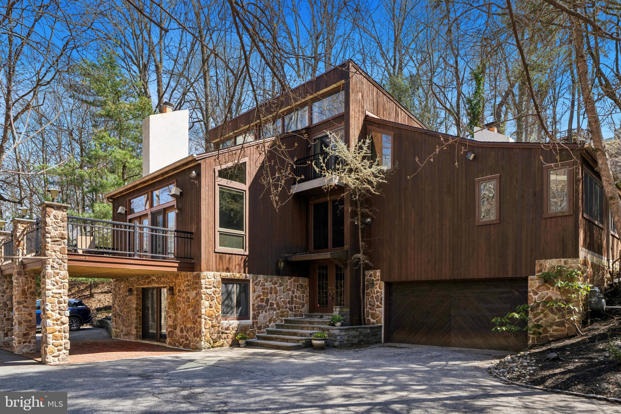 Experience unmatched luxury and privacy in this stunning home situated on a serene, nearly one-acre wooded lot, offering an exceptional living experience in the highly sought-after Lower Merion School District.  The home features 4 bedrooms, 3 full bathrooms and a stylish powder room, effortlessly combining modern design with family-friendly comfort. With convenient access to Center City Philadelphia, King of Prussia, and vibrant Manayunk, everything you need is just minutes away.

As you approach the home, wide flagstone steps lead you to the grand entrance, where a striking handmade copper portico welcomes you into a two-story foyer, complete with a dramatic domed chandelier that sets the tone for elegance. The open-concept main level is a showstopper, with recently refinished tongue-and-groove hardwood floors, expansive windows, and skylights filling the space with natural light.

The gourmet chef's kitchen is a true culinary masterpiece, featuring a premium Wolf range, a brand-new 48” refrigerator, spacious pantry, and glass-enclosed breakfast area. Seamlessly connected to the kitchen is the generous dining room, with a built-in for added functionality. Sliding doors from both the kitchen and dining room lead to the expansive wraparound patio and a private, flat backyard, surrounded by mature trees—an ideal space for relaxation or entertaining.  An electric hook-up is available for a hot tub.  French doors from the family room open to a brand-new, oversized front deck, offering tranquil views of the nearby creek and vibrant flowering trees. The family room features a large gas fireplace, a floating OLED TV, wood beams, and an abundance of glass, creating an inviting space for both entertaining and intimate gatherings.

The primary suite is a true sanctuary, complete with stained glass accents, a gas fireplace, new carpeting (2025), real wood beams, and a private balcony. The suite also features a spacious walk-in closet and a spa-like en-suite bathroom with an extra-large double vanity, a walk-in shower, and radiant heated floors.  On this level, you will find two additional nice sized bedrooms, along with a full bath.

This home also boasts three gas fireplaces—located in the living room, den, and primary suite—providing warmth and charm throughout the space.  The newly updated main-floor den offers soaring ceilings, skylights, wood beams, custom built-ins, a gas fireplace, and a wet bar with glass shelving, making it another area for both entertaining and relaxing.  A private office, accessible through the den or a separate entrance, features windows, its own HVAC system, recessed lighting, and built-in speakers.

The entry level includes a versatile bonus room (ideal for use as a den, playroom, or gym), w/sliding doors leading to the front patio, the fourth bedroom, a full bath,  a large storage closet and access to the two-car garage.

Additional features include a large, flat driveway, a whole-house generator, a new roof & skylight (12/2024), and a dedicated laundry room with updated top-of-the-line appliances, a sink, ample cabinetry, & built-in cubbies.
Surrounded by nature yet just minutes from urban amenities, this meticulously updated home on a quiet street is a rare find. Don’t miss the opportunity to make this private oasis your own!

Highlights:
• Lot Size: .84 acres (wooded &  private)
• 2-car garage (painted 3/2025) & large flat driveway
• Brand-new  (3/2025)expansive front deck w/creek & flowering tree views
• Large wraparound rear patio
• Private, flat, rear yard, New Fence (3/2025)
• Flagstone walkway & entry steps
• Soaring entryway w/handmade copper portico & dramatic domed chandelier
• Whole-house generator
• Chef’s kitchen with Wolf range & brand-new 48” refrigerator
• Real wood beams, ceiling fans, chandeliers & recessed lighting
• Laundry room w/updated top-of-the-line appliances, sink, w/2 built-in cubbies
• New roof (12/2024)
• All furniture is negotiable