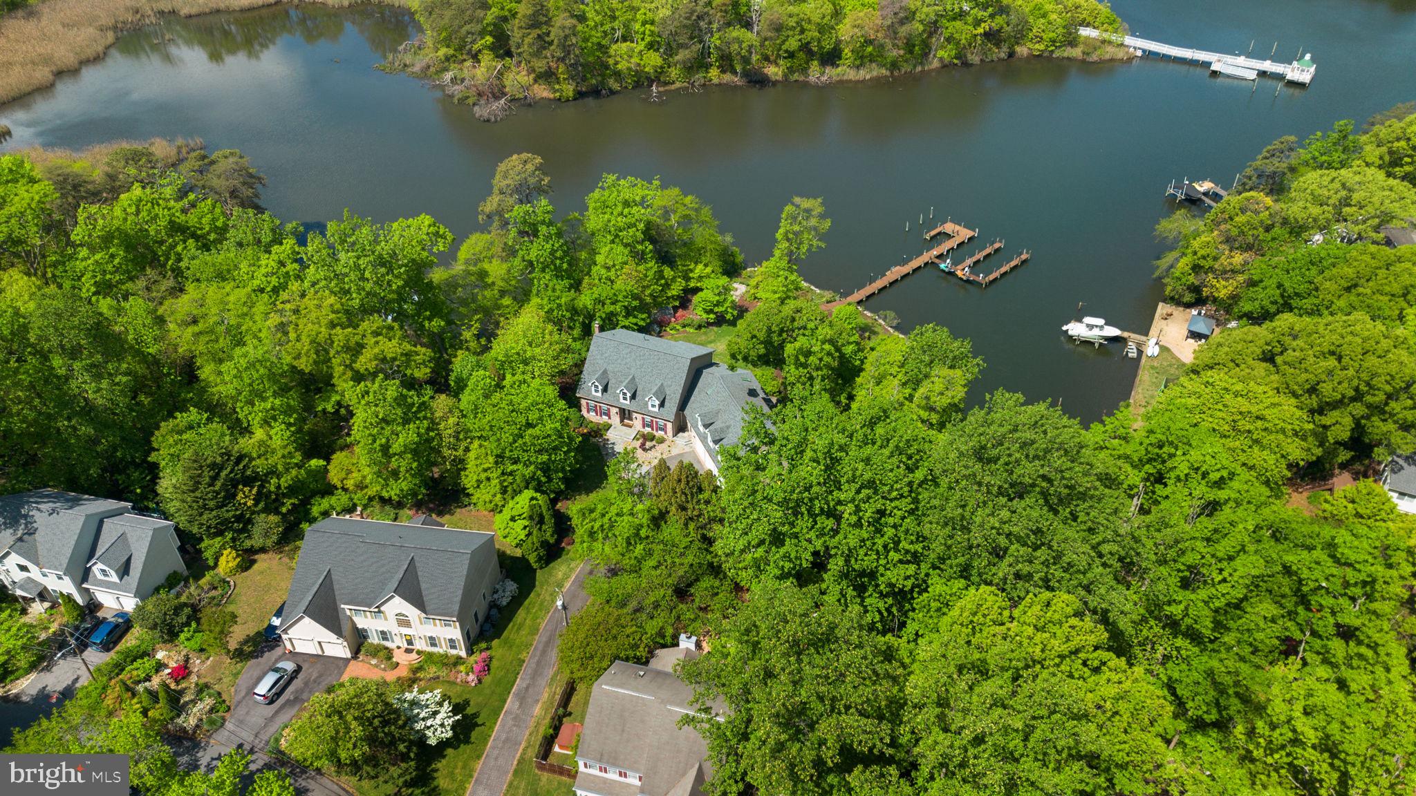 Situated in a private setting overlooking a serene cove off Cypress Creek, this exceptional waterfront property offers the perfect blend of comfort, space, and coastal living. With stunning northwest-facing views, enjoy breathtaking sunsets from multiple vantage points throughout the home. A striking stone front and attached three-car garage create an impressive first impression, while inside, bamboo hardwood flooring and thoughtfully designed living spaces blend warmth with functionality. Spanning three finished levels, the home is designed for both everyday comfort and exceptional entertaining. The main level features a dramatic two-story great room with a dual-sided fireplace extending to the outdoor living space, a formal dining room, private home office, half bath, and a desirable main-level primary suite complete with separate laundry, an oversized walk-in closet, and a luxurious super bath featuring a large shower, dual vanity, and additional closet space. The primary suite also offers direct access to the expansive rear deck. At the heart of the home is a beautifully updated gourmet kitchen, fully renovated in 2023 with a large center island and high-end appliances, including a GE Monogram refrigerator, gas cooktop with griddle, double wall ovens, Advantium oven, and Fisher & Paykel double drawer dishwasher. Recent improvements throughout include flooring, updated windows and doors, and four HVAC systems for year-round comfort. Outdoor living is equally impressive, highlighted by expansive Ipe wood decking, a SunSetter awning, gas fire pit, and an additional wood-burning fire pit tucked into the yard—creating the perfect backdrop for waterfront evenings. Adding tremendous flexibility, the property includes a private apartment above the attached three-car garage, accessible via a separate mudroom entry and rear staircase. This well-appointed space features its own kitchen, living room with fireplace, bedroom, full bath, and abundant storage. The expansive lower level adds even more versatility, complete with a large recreation/living area, a third kitchen, home gym, bedroom, full bath, and access to both glass-enclosed and screened porches. Set along 350 feet of shoreline on Cypress Creek, the property is equipped with a private pier featuring three slips (including two wider, deeper slips), two PWC lifts, plus water and electric service. With riparian rights, navigable depths, and coveted northwest-facing sunset views, it’s an ideal setting for boating, kayaking, crabbing, and fishing just moments from the Magothy River. Located within the Manhattan Beach community association, residents enjoy access to multiple beaches, a boat ramp, and clubhouse for a minimal annual fee. This is a rare opportunity to experience peaceful waterfront living with modern updates, incredible flexibility, and unforgettable views.